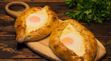 Yeni bir şehri ziyaret ettiğinde o ilk acıkma hissini yaşamayan yoktur. İşte o an hem &ccedil;ok tanıdık bir tat ararsın hem de farklı bir k&uuml;lt&uuml;r&uuml;n izlerini o yemekte g&ouml;rmek istersin. Batum, Karadeniz&rsquo;in serinliğini Kafkasya&rsquo;nın k&ouml;kl&uuml; ve baharatlı mutfak mirasıyla harmanladığı mutfağıyla sana tam da bu hissi yaşatacak lezzetleri bir arada sunuyor. Batum, sadece bir liman kenti değil, her k&ouml;şesi iştah a&ccedil;ıcı lezzetlerle dolu bir gastronomi durağı. Burada her sofra, misafirperverlik ile donatılıyor. Batum yemekleri, Acar b&ouml;lgesinin bereketli topraklarından ve derin mutfak ge&ccedil;mişinden de izler taşıyor.&nbsp; Peynirin tereyağıyla olan uyumundan, &uuml;z&uuml;m&uuml;n binlerce yıllık şarap yolculuğuna kadar uzanan se&ccedil;enekler ile Batum, her damak tadına uygun lezzetler sunuyor. Batum sokaklarında gezerken burnuna gelen tereyağı kokusunu takip etmeye ve bu eşsiz lezzetlerle tanışmaya ne dersin? Hadi bu lezzetleri birlikte keşfedelim. 1. Acar ha&ccedil;apurisi Batum denince akla ilk gelen yemek tartışmasız adjaruli khachapuri. Bu tekne şeklindeki hamur işi, ortasındaki bol peynir, tereyağı ve &uuml;zerine kırılan &ccedil;iğ yumurtayla servis ediliyor. Bu &ouml;zel pide, Karadeniz&rsquo;in dalgalarını temsil eden bol miktarda eritilmiş y&ouml;resel peynirle dolduruluyor. Anlatıya g&ouml;re fırından &ccedil;ıkmadan hemen &ouml;nce &uuml;zerine eklenen yumurta sarısı g&uuml;neşi, &uuml;zerine bırakılan tereyağı ise denizi simgeliyor. Batum&rsquo;un en modern restoranlarından en eski fırınlarına kadar her yerde bu &uuml;nl&uuml; pideleri tadabilirsin. Fırından yeni &ccedil;ıkmış sıcak hamur kokusunun ve limandan gelen serin esintinin bir araya gelerek oluşturduğu o atmosfer sayesinde Batum'da olduğunu iliklerine kadar hissedeceksin. 2. G&uuml;rc&uuml; mantısı G&uuml;rcistan&rsquo;ın ulusal yemeği olan bu dev mantılar, b&uuml;y&uuml;k hamur boh&ccedil;alarının baharatlı et harcı ve lezzetli et suyuyla pişirilmesiyle hazırlanıyor. G&uuml;rc&uuml; mantısı vejetaryenler i&ccedil;in peynirli, mantarlı veya patatesli olarak da yapılıyor. Khinkali yemenin kendine has bir tarzı da var. Geleneğe g&ouml;re &ccedil;atal kullanmak, i&ccedil;indeki değerli suyu ziyan edeceği i&ccedil;in bir hata olarak kabul ediliyor. Boh&ccedil;ayı elinle sapından tutup ters &ccedil;evirerek k&uuml;&ccedil;&uuml;k bir delik a&ccedil;malı, &ouml;nce suyunu i&ccedil;ip sonra geri kalanını yemelisin. G&uuml;rc&uuml; mutfağının kalbi sayılan khinkali, hem doyurucu hem de lezzetiyle deneyen herkes tarafından b&uuml;y&uuml;k beğeni topluyor. 3. Sinori Batum&rsquo;un en &ouml;zg&uuml;n yerel lezzetlerinden biri olan Sinori, sadeliğin ve lezzetin m&uuml;kemmel bir uyumunu sunuyor. Kurutulmuş yufka rulolarının bir fırın tepsisine dikey şekilde dizilmesiyle hazırlanan bu yemek, sarımsaklı s&uuml;zme yoğurt veya lor peyniriyle harmanlanan &ouml;zel bir karışımla fırınlanıyor. Fırından &ccedil;ıktıktan sonra &uuml;zerine gezdirilen bol miktarda kızdırılmış tereyağı ise yufkaların yumuşamasını sağlıyor. Genellikle bir iştah a&ccedil;ıcı veya yan &ouml;ğ&uuml;n olarak servis edilen sinori, yoğun aroması ve doyuruculuğuyla Batum sofralarının en geleneksel tatlarından biri. 4. Achma Klasik pastane a&ccedil;malarından &ccedil;ok farklı olan achma, G&uuml;rc&uuml; mutfağının en sabır isteyen ve en &ouml;d&uuml;llendirici lezzetlerinden biri. Achma, hazırlanış tekniği ve &ccedil;ok katmanlı yapısı nedeniyle sıklıkla "G&uuml;rc&uuml; lazanyası" olarak adlandırılıyor. Bu &ouml;zel b&ouml;rek, incecik hamur katmanlarının haşlanıp aralarına bolca y&ouml;resel peynir (sulguni) ve eritilmiş tereyağı eklenerek fırınlanması ile hazırlanıyor. Dışı hafif &ccedil;ıtır, i&ccedil;i ise peynirin ve tereyağının kusursuz uyumuyla yumuşacık kalan bu lezzet, Batum fırınlarında ger&ccedil;ek bir ziyafet sunuyor. Yoğun dokusuyla &uuml;nl&uuml; olan bu yemek, Batum gastronomi turlarının en "karbonhidrat dostu" lezzetleri arasında yer alıyor. 5. Cevizli patlıcan ruloları Badrijani nigvzit, G&uuml;rc&uuml; sofralarının en estetik başlangı&ccedil;larından biri. Bu lezzetli rulolar, kızarmış ince patlıcan dilimlerinin i&ccedil;ine sarılan nefis bir ceviz ezmesiyle hazırlanıyor. &Ouml;zel har&ccedil;, d&ouml;v&uuml;lm&uuml;ş ceviz, sarımsak, sirke ve G&uuml;rc&uuml; mutfağının imza baharatları (mavi &ccedil;emen otu ve kişniş) ile harmanlanıyor. Har&ccedil;, patlıcanın yumuşak dokusuyla m&uuml;kemmel bir lezzet kontrastı oluşturuyor. Genellikle soğuk servis edilen badrijani nigvzit rulolarının &uuml;zerine serpiştirilen nar taneleri de hem tabağa g&ouml;rsellik ekliyor hem de her ısırıkta damağa ferahlatıcı bir ekşilik veriyor. Batum&rsquo;da bir akşam yemeğine başlamanın en klasik yolu olan bu meze, ayrıca vegan ve vejetaryen dostu. {insightBoxStart}İpucu:&nbsp;Batum&rsquo;un eşsiz sofralarında yerin şimdiden hazır. Bu lezzet yolculuğuna birlikte &ccedil;ıkmak istersen en iyi otel fiyatlarını tek bir yerde g&ouml;rmek, se&ccedil;eceğin otel hakkında bilgi almak ve saniyeler i&ccedil;inde rezervasyon yapmak i&ccedil;in ENUYGUN'da&nbsp;Batum otelleri&nbsp;araştırmasına başlayabilirsin.{insightBoxEnd} {hotel_search_form_banner} 6. Pkhali Pkhali, G&uuml;rc&uuml; sofralarının hem en sağlıklı hem de en g&ouml;z alıcı başlangı&ccedil;larından biri. Bu geleneksel ezme, haşlanmış ve ince kıyılmış sebzeleri, zengin bir ceviz sosuyla buluşturarak eşsiz bir lezzet sunuyor. Ispanak, pancar, pırasa veya lahana gibi farklı sebzelerle hazırlanan pkhali, sarımsak, sirke ve G&uuml;rc&uuml; mutfağının vazge&ccedil;ilmezi olan kişniş gibi baharatlarla da lezzetlendiriliyor. Renk renk dizilen sunumuyla tabağa g&ouml;rsel bir canlılık katan pkhali, &uuml;zerine eklenen parlak nar taneleriyle de hem ferah hem de iştah a&ccedil;ıcı. 7. Churchkhela (&Ccedil;er&ccedil;hel) Batum sokaklarında y&uuml;r&uuml;rken karşına &ccedil;ıkacak, renkli ve uzun kandilleri andıran &uuml;nl&uuml; tatlı churchkhela, denemeye değer bir yerel lezzet. İ&ccedil;erdiği yoğun ceviz, fındık ve &uuml;z&uuml;m şırasının (veya nar, dut gibi meyve sularının) karışımı sayesinde bu tatlı, enerji verici &ouml;zelliğiyle dikkat &ccedil;ekiyor. Bu &ouml;zelliği tatlıya d&uuml;nya &ccedil;apında "G&uuml;rc&uuml; Snickers'ı" lakabını kazandırmış. İpe dizilen yemişlerin, unla kıvam kazanan meyve suyuna batırılıp ardından g&uuml;neşte kurutulmasıyla elde edilen bu lezzet, tamamen doğal, katkısız ve olduk&ccedil;a doyurucu. 8. Pelamushi G&uuml;rc&uuml; mutfağının en geleneksel ve doğal tatlılarından biri olan Pelamushi, &ouml;zellikle &uuml;z&uuml;m hasadı d&ouml;neminde &ccedil;ok ilgi g&ouml;r&uuml;yor. Pelamushi, koyu renkli &uuml;z&uuml;m suyunun (badagi), mısır unu ve bazen buğday unuyla koyulaşana kadar kaynatılması sonucu elde ediliyor. Soğuduktan sonra j&ouml;le kıvamını alan bu puding, &uuml;zerine bolca ceviz i&ccedil;i serpilerek servis ediliyor. Hem hafif hem de meyvemsi bir tat arayanlar i&ccedil;in pelamushi, Batum&rsquo;daki en doğru tercih. 9. G&uuml;rc&uuml; şarapları G&uuml;rcistan, 8000 yıllık ge&ccedil;mişiyle şarabın eski &uuml;retim yerlerinden biri olarak kabul ediliyor. Batum ise bu şarap mirasını en iyi g&ouml;rebileceğin şehirlerden biri. Şehirdeki mahzenlerde geleneksel qvevri (toprak k&uuml;p) y&ouml;ntemiyle &uuml;retilen kehribar renkli beyaz şarapları veya derin aromalı kırmızı saperavi şaraplarını deneyebilirsin. Batı G&uuml;rcistan&rsquo;da yaygın, hafif ve meyvemsi bir beyaz şarap olan tsolikouri ise Batum'un deniz havasına en yakışan yerel şarap se&ccedil;eneği. 10. Chacha G&uuml;rc&uuml;lerin "sıvı ateşi" olarak adlandırdığı chacha, &uuml;z&uuml;m posasından damıtılan olduk&ccedil;a sert ve şeffaf bir i&ccedil;ki. Genellikle %40 ile %65 arasında alkol oranına sahip olan chacha, G&uuml;rc&uuml; misafirperverliğinin ve uzun sofra eğlencelerinin vazge&ccedil;ilmezi. Batum'da hem bu i&ccedil;eceğin tadına bakabilir hem de sahil şeridindeki meşhur Chacha Kulesi'ni ziyaret ederek bu i&ccedil;eceğin yerel k&uuml;lt&uuml;rdeki &ouml;nemini daha iyi anlayabilirsin. {{campaignsSlider}} 11. Borano Batum&rsquo;un en karakteristik lezzetlerinden biri olan borano, peynir tutkunları i&ccedil;in adeta bir lezzet ş&ouml;leni. Diğer Batum yemeklerinin aksine hamur i&ccedil;ermeyen bu tarif, temel olarak y&ouml;resel Acar peynirinin &uuml;zerine bol miktarda kızdırılmış ve k&ouml;p&uuml;rm&uuml;ş tereyağı d&ouml;k&uuml;lmesi ile hazırlanıyor. Bazı tariflerde yumurta da eklenebiliyor. Geleneksel olarak toprak kaplarda (ketsi) servis edilen borano, tereyağının sıcaklığıyla eriyen peynirin uzayan dokusu ve yoğun aromasıyla tam bir enerji deposu. Genellikle taze mısır ekmeğiyle birlikte t&uuml;ketilen bu yemek, sadeliğin en zengin halini temsil ediyor. 12. Lagidze gazozları Alkol kullanmayanlar veya nostaljik bir lezzet arayanlar i&ccedil;in ideal olan Lagidze gazozları, G&uuml;rcistan'ın en ikonik markası. Tamamen doğal meyve şurupları ve maden suyuyla hazırlanan bu &uuml;nl&uuml; gazozlar, tarhun, armut, limon ve hatta &ccedil;ikolata gibi farklı se&ccedil;eneklere sahip. &Ouml;zellikle yeşil rengiyle dikkat &ccedil;eken tarhunlu gazozlar, Batum sokaklarında sıcak yaz aylarında serinlemek i&ccedil;in i&ccedil;ebileceğin en karakteristik ve ferahlatıcı i&ccedil;ecek. Batum&rsquo;un birbirinden g&uuml;zel bu lezzetlerini denemek ve keyifli bir rota oluşturmak i&ccedil;in G&uuml;rcistan&rsquo;a nasıl gidilir? yazımızı inceleyebilirsin.