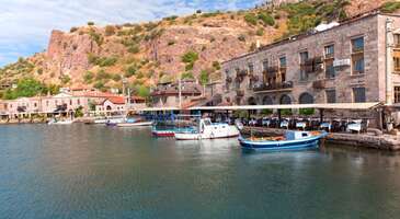 Assos, antik &ccedil;ağların mistik atmosferi ile Ege'nin berrak sularını buluşturan eşsiz bir yer. Tarihi dokusuyla insanları b&uuml;y&uuml;leyen Assos, aynı zamanda masmavi denizi ve huzur dolu koylarıyla denize girmek isteyenler i&ccedil;in adeta bir cennet. Kaz Dağları'nın eteklerinden s&uuml;z&uuml;len serin suların Ege ile kucaklaştığı Assos'ta kalabalıktan uzak, sakin ve doğal plajlardan hareketli plaj kul&uuml;plerine kadar her zevke uygun bir se&ccedil;enek bulmak m&uuml;mk&uuml;n.&nbsp; Ben Assos&rsquo;a arkadaşımın tavsiyesi &uuml;zerine gittim. İstanbul&rsquo;dan otob&uuml;sle yaklaşık 6 saatte K&uuml;&ccedil;&uuml;kkuyu&rsquo;ya gittim. Oradan minib&uuml;slerle kolay bir şekilde Assos&rsquo;a ge&ccedil;tim. Bunun yanında Ayvacık otob&uuml;sleri de Assos&rsquo;a gidiyor. Aynı şekilde oradan da minib&uuml;sler bulunuyor. Assos&rsquo;un denizine, havasına ve k&uuml;lt&uuml;rel atmosferine bayıldım. Tatilimden notlarla birlikte Assos&rsquo;ta denize girilecek yerleri birlikte keşfedelim.&nbsp; 1. Kadırga Koyu Benim Assos&rsquo;ta denize girmek i&ccedil;in tercih ettiğim yer Kadırga Koyu oldu. Otelimi de yine bu koyda ayarladım. Otelime ait plajda Kuzey Ege&rsquo;nin masmavi sularında y&uuml;zd&uuml;m. Deniz g&uuml;n&uuml;n her saati aynı berraklıkta oluyor. Beni şaşırtan bir diğer detay ise denizin aniden derinleşmesi oldu. B&ouml;lgede sık sık kullanılan &ldquo;7 adımda boy&rdquo; deyimini gittiğimde daha iyi anladım. Koyda bulunan &ccedil;ok sayıda otel ve kamp alanının kendine ait plajı bulunuyor. Ancak otel misafiri olmasan da g&uuml;n&uuml;birlik giriş yapabilirsin. Kadırga Koyu hem mavi hem de yeşilin bir arada yer aldığı huzur bir atmosfer vadediyor.&nbsp; Adını Osmanlı D&ouml;nemi&rsquo;nin k&uuml;rekli kadırga gemilerinden alıyor. Benim deniz keyfinden sonra en b&uuml;y&uuml;lendiğim an, sahil kenarında yer alan restoranlarda nefes kesen g&uuml;n batımı eşliğinde yediğim akşam yemeği oldu. Kartpostallara konu olarak bir g&uuml;zelliğe sahip olan g&uuml;n batımına deniz ve zeytin ağa&ccedil;ları eşlik ediyor. Koy boyunca sıralanan balık restoranları ve kafelerde taze deniz &uuml;r&uuml;nlerini ve meşhur Assos zeytinyağlı mezelerini deneyebilirsin.&nbsp; Konum Linki {calismasaatleri}Kadırga Plajı giriş &uuml;cretleri Halk plajı b&ouml;l&uuml;m&uuml; &uuml;cretsiz Şezlong ve şemsiye kişi başı 200 TL Kadırga Plajı&rsquo;ndaki beachler Kavala Beach Rasa&amp;Me Camping Beach Club Troy Beach Assos Lion Beach Assos Club Beyaz DC Club Assos Eden Beach Antic Olea Beach &amp;Caravan Tesis imk&acirc;nları Duş ve soyunma kabinleri Tuvalet Şezlong ve şemsiye kiralama hizmeti &Ccedil;evrede restoranlar ve kafeler Market ve alışveriş imkanı Ara&ccedil; otoparkı.{/calismasaatleri} {insightBoxStart}Yazar Notu: Kadırga Koyu&rsquo;nda plaj taşlık olduğundan yanına deniz ayakkabısı almayı unutma.{insightBoxEnd} 2. Assos Antik Liman&nbsp; Assos&rsquo;ta tarihle i&ccedil; i&ccedil;e deniz keyfi yapabileceğin en b&uuml;y&uuml;leyici noktalarından biri de Antik Liman. Antik Liman&rsquo;ın kendine ait bir kumsalı olmasa da restore edilmiş tarihi taş iskelelerden, limana plajlardan veya &ccedil;evre otellerin &ouml;n&uuml;ndeki platformlardan denize girilerek bu eşsiz deneyimi yaşayabilirsin. Burada hem doyasıya y&uuml;zebilir hem de binlerce yıllık tarihin tam kalbinde dinlenebilirsin. Athena Tapınağı'nın g&ouml;lgesinde uzanan eşsiz liman, antik &ccedil;ağlardan kalan taş binaları ve kendine has atmosferiyle adeta bir a&ccedil;ık hava m&uuml;zesini andırıyor. Limanda bir yandan Ege'nin masmavi ve serin sularının tadını &ccedil;ıkarırken, diğer yandan Aristo'nun y&uuml;r&uuml;d&uuml;ğ&uuml;, filozofların ders verdiği toprakları keşfedebilirsin. Assos Antik Liman'ın denizi, taşlık ve kayalık bir tabana sahip. Su ise berrak ve temiz olduğu i&ccedil;in şnorkelli dalışlar yaparak b&uuml;y&uuml;leyici su altı d&uuml;nyasını keşfedebilirsin. G&uuml;n boyunca deniz ve g&uuml;neşin keyfini &ccedil;ıkardıktan sonra akşam saatlerinde ise Athena Tapınağı'nın ışıklandırılmış sil&uuml;etine karşı, dalga sesleri eşliğinde Ege mutfağının lezzetlerini tadarak Assos Antik Liman'ın atmosferini doyasıya yaşayabilirsin. Konum Linki {calismasaatleri}Assos Antik Liman giriş &uuml;cretleri Halk plajı b&ouml;l&uuml;m&uuml; &uuml;cretsiz Şezlong ve şemsiye kişi başı 250 TL Tesis imk&acirc;nları Duş ve soyunma kabinleri Tuvalet Şezlong ve şemsiye kiralama hizmeti &Ccedil;evrede restoranlar ve kafeler Market ve alışveriş imkanı Ara&ccedil; otoparkı.{/calismasaatleri} {insightBoxStart}Yazar Notu: Denizin tadını &ccedil;ıkardıktan sonra Behramkale&rsquo;nin dar sokaklarında gezinti yapabilir, antik Athena Tapınağı'nın ihtişamını g&ouml;rebilir veya Assos limanındaki balık&ccedil;ı teknelerinin karşısında keyifli bir akşam yemeği yiyebilirsin.{insightBoxEnd} 3. Sokak Ağzı Plajı Assos'un kalabalığından uzakta, doğayla i&ccedil; i&ccedil;e bir deniz g&uuml;n&uuml; yaşamak isteyenler i&ccedil;in Sokak Ağzı Plajı, saklı kalmış bir cennet. Zeytin ağa&ccedil;larının yeşiliyle Ege'nin mavisinin kucaklaştığı plaj, yıl boyunca huzur dolu bir atmosfere sahip. Midilli Adası'nın manzarasının s&uuml;slediği plaj, geniş ve uzun kumsalı ve berrak deniziyle Assos&rsquo;un tadını &ccedil;ıkarmak i&ccedil;in ideal.&nbsp; Hem ruhunu dinlendirmek hem de Ege'nin otantik dokusunu hissetmek isteyenler i&ccedil;in uygun olan Sokak Ağzı Plajı, bakir doğasını korumasının yanı sıra ziyaret&ccedil;ilerine konforlu bir tatil imkanı da sunuyor. Sahil boyunca sıralanan butik oteller, aile pansiyonları ve kamp alanlarında her b&uuml;t&ccedil;eye uygun konaklama se&ccedil;enekleri bulabilirsin. Kıyıdaki salaş balık&ccedil;ı lokantaları ve kafeler de Ege mutfağının en g&uuml;zel lezzetlerini tatilcilerle buluşturuyor.&nbsp; Konum Linki {calismasaatleri}Sokak Ağzı Plajı giriş &uuml;cretleri Halk plajı b&ouml;l&uuml;m&uuml; &uuml;cretsiz Tesis imk&acirc;nları Şezlong ve şemsiye kiralama hizmeti &Ccedil;evrede restoranlar ve kafeler Market ve alışveriş imkanı Ara&ccedil; otoparkı.{/calismasaatleri} {insightBoxStart}Yazar Notu: Plajın arkasında &ccedil;am ağa&ccedil;ları arasına gizlenen k&uuml;&ccedil;&uuml;k balık restoranlarında taze ızgara balık, ahtapot, Ege otlarıyla hazırlanmış mezeler ve deniz sesi eşliğinde yorgunluk atabilirsin.{insightBoxEnd} 4. Yeşil Liman Koyu Behramkale'nin antik dokusunun hemen yanındaki Assos Antik Limanı'nın kuzeybatısında gizlenen Yeşil Liman Koyu, adını denizin b&uuml;y&uuml;leyici z&uuml;mr&uuml;t yeşili tonundan alıyor. Etrafını saran yemyeşil &ccedil;am ormanları ve antik taş ocaklarının dramatik manzarasıyla tam bir doğa harikası olan koy, sakinlik arayanlar i&ccedil;in harika bir ka&ccedil;ış noktası. Plaj, iri &ccedil;akıl taşlarıyla kaplı ve suyun kristal berraklığı, antik d&ouml;nemde buradan &ccedil;ıkarılan mermer blokların h&acirc;l&acirc; su altında g&ouml;r&uuml;lebilen kalıntılarıyla b&uuml;y&uuml;leyici bir dalış deneyimi sunuyor. Meltem r&uuml;zg&acirc;rlarının estiği yaz g&uuml;nlerinde bile korunaklı yapısı sayesinde sakin kalan koy, tekne gezilerinin de g&ouml;zdesi. Yeşil Liman Koyu, Assos&rsquo;un tarihi dokusuyla i&ccedil; i&ccedil;e ge&ccedil;miş mistik bir atmosfere sahip. Yeşil Liman Koyu&rsquo;nda mutlaka Midilli Adası&rsquo;nın silueti eşliğinde g&uuml;n batımını izlemeni &ouml;neririz. Konum Linki {calismasaatleri}Yeşil Liman Koyu giriş &uuml;cretleri Halk plajı b&ouml;l&uuml;m&uuml; &uuml;cretsiz Şezlong ve şemsiye kişi başı 200 TL Tesis imk&acirc;nları Kamp ve karavan i&ccedil;in uygun alanları Piknik yapmak i&ccedil;in uygun alanlar Balık tutma noktaları Ara&ccedil; parkı i&ccedil;in uygun park alanları Doğa y&uuml;r&uuml;y&uuml;ş&uuml; i&ccedil;in patikalar.{/calismasaatleri} {insightBoxStart}Yazar Notu: Yeşil Liman Koyu&rsquo;na karadan ulaşım biraz zor. En rahat erişim, Assos Antik Liman&rsquo;dan (Behramkale iskelesi) 10-15 dakikalık taş patika y&uuml;r&uuml;y&uuml;ş&uuml;, arazi aracı veya tekneyle m&uuml;mk&uuml;n.{insightBoxEnd} 5. Sivrice Koyu Assos&rsquo;un huzurlu tatil cenneti olan Sivrice Koyu, tertemiz denizi Assos'un tarihi atmosferiyle birleştirerek &ouml;zel bir deneyim yaşatıyor. Koy, &ouml;zellikle kalabalıktan uzak, sakin bir tatil arayanlar tarafından tercih ediliyor. Sahil boyunca sıralanan taş evler ve k&uuml;&ccedil;&uuml;k pansiyonlar, tatilcilere samimi ve sıcak bir konaklama ortamı sunuyor. Temiz plajları, masmavi denizi ve zeytin ağa&ccedil;larıyla da dikkat &ccedil;eken Sivrice Koyu, hem deniz tutkunları hem de doğa tutkunlarını kendine &ccedil;ekiyor.&nbsp;&nbsp; Koyunun en dikkat &ccedil;ekici &ouml;zelliği ise g&uuml;n sonunda oluşan b&uuml;y&uuml;leyici manzara. Sivrice Koyu'ndan karşıdaki Midilli Adası'nı net bir şekilde g&ouml;rebilir, kızıl g&uuml;n batımlarında romantik anlar yaşayabilirsin. Koy &ccedil;evresinde hizmet veren yerel balık restoranlarında ise taze deniz &uuml;r&uuml;nleri tadabilir veya Ege mutfağının eşsiz lezzetlerini deneyimleyerek g&uuml;n&uuml;n yorgunluğunu atabilirsin. Konum Linki {calismasaatleri}Sivrice Koyu giriş &uuml;cretleri &Uuml;cretsiz Tesis imk&acirc;nları Tuvalet &Ccedil;evrede restoranlar ve kafeler Kamp ve karavan i&ccedil;in uygun alanları Piknik yapmak i&ccedil;in uygun alanlar Balık tutma noktaları Ara&ccedil; parkı i&ccedil;in uygun park alanları Doğa y&uuml;r&uuml;y&uuml;ş&uuml; i&ccedil;in patikalar.{/calismasaatleri} {insightBoxStart}Yazar Notu: Sivrice Koyu&rsquo;na yakın Assos Antik Kenti, Behramkale K&ouml;y&uuml;, Kaz Dağları gibi tarihi ve doğal g&uuml;zellikleri y&uuml;r&uuml;y&uuml;şlerle kolayca keşfe &ccedil;ıkabilirsin.{insightBoxEnd} {insightBoxStart}İpucu: En iyi otel fiyatlarını tek bir yerde g&ouml;rmek, se&ccedil;eceğin otel hakkında bilgi almak ve saniyeler i&ccedil;inde rezervasyon yapmak i&ccedil;in ENUYGUN'da Assos otelleri araştırmasına başlayabilirsin.{insightBoxEnd} {hotel_search_form_banner} 6. Karadiken Koyu Assos'un b&uuml;y&uuml;leyici sahil şeridinde keşfedilmeyi bekleyen gizli bir hazine olan Karadiken Koyu, doğallığı ve sakinliğiyle &ouml;ne &ccedil;ıkıyor. Pop&uuml;ler tatil rotalarının dışında kalan bakir koy, Assos ile Babakale arasındaki zeytin ağa&ccedil;larının yeşili i&ccedil;inde saklanıyor. Ulaşımın zor olması buranın el değmemiş atmosferini korumasına yardımcı oluyor. Karadiken'e vardığında ise seni &ccedil;akıl taşlarıyla s&uuml;sl&uuml; k&uuml;&ccedil;&uuml;k bir sahil ve akvaryumu andıran berrak turkuaz rengi bir deniz karşılayacak.&nbsp; Karadiken Koyu&rsquo;nda herhangi bir işletme veya tesis bulunmaması da koyda sessizce doğayla baş başa dinlenmeye olanak tanıyor. Denizin altındaki zengin yaşam, şnorkelle dalış yapmak i&ccedil;in harika fırsatlar sunarken, etrafı saran yemyeşil tepeler ise kısa doğa y&uuml;r&uuml;y&uuml;şleri i&ccedil;in uygun. &Ouml;zellikle sabah saatlerinde hissedilen huzur ve g&uuml;n batımlarındaki b&uuml;y&uuml;leyici renk c&uuml;mb&uuml;ş&uuml;, Karadiken Koyu'nu eşsiz kılıyor. Konum Linki {calismasaatleri}Karadiken Koyu giriş &uuml;cretleri Halk plajı b&ouml;l&uuml;m&uuml; &uuml;cretsiz Tesis imk&acirc;nları Kamp ve karavan i&ccedil;in uygun alanları Piknik yapmak i&ccedil;in uygun alanlar Balık tutma noktaları Ara&ccedil; parkı i&ccedil;in uygun park alanları Doğa y&uuml;r&uuml;y&uuml;ş&uuml; i&ccedil;in patikalar.{/calismasaatleri} 7. Apollon Plajı Assos'un b&uuml;y&uuml;leyici atmosferinde denize girilebilecek en &ouml;zel noktalardan Apollon Plajı, berrak suların antik mirasla i&ccedil; i&ccedil;e ge&ccedil;tiği b&uuml;y&uuml;leyici bir yer. Adını antik d&ouml;nemin &ouml;nemli tanrılarından Apollon'dan alan plaj, taşlık bir yapıya sahip olmasına rağmen, denizin inanılmaz berraklığı ve serinliği, sıcak yaz g&uuml;nlerinde ferahlamak isteyenler i&ccedil;in ideal. Plajın &ccedil;evresindeki doğal g&uuml;zellikler ve huzurlu atmosfer de yılın yorgunluğunu atmak isteyenleri buraya &ccedil;ekiyor. Apollon Plajı&rsquo;nda sadece denize girmekle kalmayıp &ccedil;evredeki tarihi dokuyu da keşfedebilirsin. Assos Antik Kenti'ne &ccedil;ok yakın olan plajdan antik tiyatro ve Athena Tapınağı gibi &ouml;nemli yapılara kolayca gidebilirsin. G&uuml;neşin batışı sırasında da Ege Denizi'nin tablo g&uuml;zelliğindeki manzarasını izleyerek Apollon Plajı'nda romantik anlar yaşayabilirsin.&nbsp; Konum Linki {calismasaatleri}Apollon Plajı giriş &uuml;cretleri &Uuml;cretsiz Tesis imk&acirc;nları Kamp ve karavan i&ccedil;in uygun alanları Piknik yapmak i&ccedil;in uygun alanlar Balık tutma noktaları Ara&ccedil; parkı i&ccedil;in uygun park alanları Doğa y&uuml;r&uuml;y&uuml;ş&uuml; i&ccedil;in patikalar.{/calismasaatleri} {insightBoxStart}Yazar Notu: Plaja yakın konumlarda y&ouml;resel lezzetleri tadabileceğin restoranlar ve konaklama imkanları bulabilirsin.{insightBoxEnd} 8. Koruoba sahili Assos'un vahşi cenneti olan Koruoba, Behramkale'nin batısında, antik taş ocakları ile &ccedil;am ormanlarının kucaklaştığı sahiliyle dikkat &ccedil;ekiyor. Koruoba sahili, Assos'un en bakir ve el değmemiş k&ouml;şelerinden biri. Ulaşımı biraz zor olan bu gizemli koy, tam bir doğa harikası ve sessizlik arayanlar i&ccedil;in ideal. Sahil, iri &ccedil;akıl taşları ve koyu kum karışımı, deniz ise &ouml;zellikle sabah saatlerinde turkuazdan laciverte uzanan b&uuml;y&uuml;leyici renk tonlarıyla adeta bir ressam paletini andırıyor. Sahilin etrafını saran dik yama&ccedil;lar ve yemyeşil ormanlar, koyu r&uuml;zg&acirc;rlardan koruduğu i&ccedil;in kamp ve piknik i&ccedil;in uygun bir ortam yaratıyor. Su altında ise antik d&ouml;nemden kalma devasa taş bloklarını şnorkelli dalışlar yaparak g&ouml;rebilirsin. Koruoba sahilinin en b&uuml;y&uuml;k &ouml;zelliği ise kalabalıklardan uzakta sadece dalga ve martı sesleri eşliğinde keyifle y&uuml;zmek. Midilli Adası&rsquo;nın g&uuml;zel manzarası ve &ouml;zellikle g&uuml;n batımında sahili saran altın ışıklar da romantik bir atmosfer yaratarak Koruoba sahilini &ccedil;iftler i&ccedil;in &ouml;zel bir yer yapıyor. Konum Linki {calismasaatleri}Koruoba sahili giriş &uuml;cretleri &Uuml;cretsiz Tesis imk&acirc;nları Kamp ve karavan i&ccedil;in uygun alanları Piknik yapmak i&ccedil;in uygun alanlar Balık tutma noktaları Ara&ccedil; parkı i&ccedil;in uygun park alanları Doğa y&uuml;r&uuml;y&uuml;ş&uuml; i&ccedil;in patikalar.{/calismasaatleri} {insightBoxStart}Yazar Notu:&nbsp;Sahilde herhangi bir tesis bulunmadığı i&ccedil;in gelirken Behramkale k&ouml;y&uuml; veya Assos Limanı&rsquo;ndan yiyecek ve i&ccedil;ecek alabilir, &ccedil;am ağa&ccedil;larının g&ouml;lgesinde kamp yaparak yılın yorgunluğunu atabilirsin.{insightBoxEnd} 9. İskele Koyu Ege Denizi'nin huzur dolu atmosferini deneyimlemek isteyenler i&ccedil;in İskele Koyu da keşfedilmeye değer. Antik Assos Kenti&rsquo;nin eteklerinde yer alan bu k&uuml;&ccedil;&uuml;k koy, tarihi ve doğal g&uuml;zellikleri bir arada sunuyor. Eski taşların restore edilmesiyle tasarlanan iskele b&ouml;lgesi, nostaljik atmosferiyle dikkat &ccedil;ekiyor. Koyun berraklığı ve serin suları da şnorkelli dalışlar yapmak i&ccedil;in &ccedil;ok uygun. Ayrıca sahilde g&uuml;neşlenirken Midilli Adası'na kadar uzanan masmavi manzaranın keyfini &ccedil;ıkarabilirsin. G&uuml;n batımında İskele Koyu, b&uuml;y&uuml;leyici renk tonlarına b&uuml;r&uuml;nerek romantik bir atmosfer yaratarak fotoğraf&ccedil;ılar i&ccedil;in benzersiz kareler yakalama fırsatı veriyor. Tarih, doğa ve huzur bir arada sunan İskele Koyu, lezzetli Ege mutfağı deneyimi yaşamak isteyenler i&ccedil;in de ideal. Taze balık, zeytinyağlı mezeler ve y&ouml;resel tatlar eşliğinde yerel restoranlarda keyifli bir mola verebilirsin. Konum Linki {calismasaatleri}İskele Koyu giriş &uuml;cretleri Halk plajı b&ouml;l&uuml;m&uuml; &uuml;cretsiz Tesis imk&acirc;nları Duş ve soyunma kabinleri Tuvalet Şezlong ve şemsiye kiralama hizmeti &Ccedil;evrede restoranlar ve kafeler Market ve alışveriş imkanı Ara&ccedil; otoparkı.{/calismasaatleri} {insightBoxStart}Yazar Notu:&nbsp;İskele Koyu&rsquo;ndan yukarıya doğru kısa bir y&uuml;r&uuml;y&uuml;şle Assos Antik Kenti'ne ulaşılabilir, Athena Tapınağı'ndan Ege Denizi'ne uzanan panoramik manzaranın tadını &ccedil;ıkarabilirsin.{insightBoxEnd} {{campaignsSlider}} Bonus: Babakale Akliman Koyu Assos&rsquo;a yaklaşık 40 km uzaklıktaki keşfedilmeye değer incilerinden biri olan Akliman Koyu, Babakale&rsquo;nin yanı başında konforlu bir deniz keyfi yaşatıyor. B&ouml;lgedeki bir&ccedil;ok taşlık ve kayalık koyun aksine Akliman, boydan boya uzanan geniş ve altın rengi kumsalıyla dikkat &ccedil;ekiyor. Yavaş&ccedil;a derinleşen koy, &ouml;zellikle &ccedil;ocuklu aileler ve sakin bir y&uuml;zme deneyimi arayanlar i&ccedil;in ideal. R&uuml;zg&acirc;ra kapalı yapısı sayesinde genellikle dalgasız olan deniz, bir havuz hissi yaratıyor ve g&uuml;n boyu g&uuml;venle y&uuml;zme imk&acirc;nı tanıyor. Doğal g&uuml;zelliğini korumayı başaran Akliman Koyu, ziyaret&ccedil;ilerin temel ihtiya&ccedil;larını karşılayacak olanaklara da sahip. Sahil kenarında bulunan birka&ccedil; k&uuml;&ccedil;&uuml;k işletme, şezlong ve şemsiye kiralama hizmetinin yanı sıra serinletici i&ccedil;ecekler ve atıştırmalıklar da sunuyor. Kalabalıktan uzakta, Ege'nin &uuml;nl&uuml; meltemleri eşliğinde kitabını okuyup dinlenebileceğin Akliman Koyu, muhteşem denizi ve Babakale'nin tarihi atmosferiyle keşfedilmeye değer. Konum Linki {calismasaatleri}Akliman Koyu giriş &uuml;cretleri Halk plajı b&ouml;l&uuml;m&uuml; &uuml;cretsiz Şezlong ve şemsiye kişi başı 250 TL - 400 TL arası Tesis imk&acirc;nları Duş ve soyunma kabinleri Tuvalet Şezlong ve şemsiye kiralama hizmeti Kamp ve karavan alanları &Ccedil;evrede restoranlar ve kafeler Market ve alışveriş imkanı Ara&ccedil; otoparkı.{/calismasaatleri} {insightBoxStart}Yazar Notu: &nbsp;Akliman Koyu&rsquo;na taksilerle veya her saat bulabileceğin minib&uuml;slerle kolayca ge&ccedil;ebilirsin.{insightBoxEnd} Deniz keyfinin ardından b&ouml;lgedeki tarih&icirc; ve k&uuml;lt&uuml;rel yerleri keşfetmek i&ccedil;in Assos&rsquo;ta gezilecek yerler yazımızı da inceleyebilirsin.