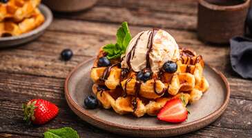 Biliyoruz, bazen bir koku seni hi&ccedil; bilmediğin yerlere s&uuml;r&uuml;kler ve "iyi ki buradayım" dersin. Bel&ccedil;ika, bu anları sık&ccedil;a yaşayacağın rotalardan biri. Br&uuml;ksel'in r&uuml;zgarlı sokaklarında y&uuml;r&uuml;rken burnuna gelen kokular kafanı karıştırabilir. Peki bu karışıklığı lezzete d&ouml;n&uuml;şt&uuml;rmeye ne dersin? Bel&ccedil;ika mutfağı, Fransız tekniklerini ve doyurucu Alman porsiyonlarını bir araya getiren karakteristik bir mutfak. Gastronomi d&uuml;nyasında devleşen Bel&ccedil;ika, damak tadına d&uuml;şk&uuml;nler i&ccedil;in adeta bir cennet. Br&uuml;ksel&rsquo;in g&ouml;rkemli meydanlarını saran taze pasta ve &ccedil;ikolata kokularından, Orta &Ccedil;ağ atmosferini koruyan Brugge sokaklarındaki dumanı t&uuml;ten midye tencerelerine kadar her k&ouml;şe başında seni ayrı bir lezzet bekliyor. Bel&ccedil;ika, Kuzey Denizi&rsquo;nin bereketiyle beslenen mutfağı, manastır biraları ve d&uuml;nyanın en kaliteli &ccedil;ikolataları ile hem &ccedil;ok tanıdık hem de şaşırtıcı derecede &ouml;zg&uuml;n bir gastronomi yolculuğu vaat ediyor. 1. Moules-Frites Bel&ccedil;ika mutfağının mill&icirc; sembol&uuml; olarak kabul edilen moules-frites, denizden gelen bir ziyafet. Moules-frites, Kuzey Denizi&rsquo;nden toplanan siyah kabuklu midyelerin beyaz şarap, tereyağı, kereviz sapı, soğan ve taze maydanoz ile derin tencerelerde buğulanmasıyla hazırlanıyor. Bu lezzet ş&ouml;leninin en b&uuml;y&uuml;k tamamlayıcısı ise Bel&ccedil;ika usul&uuml;, dışı &ccedil;ıtır i&ccedil;i yumuşak iki kez kızartılmış patates kızartmaları. Bel&ccedil;ikalılar i&ccedil;in tencerenin dibinde kalan aromatik suyu ekmekle veya patatesle t&uuml;ketmek de bir rit&uuml;el. Br&uuml;ksel&rsquo;in sahil kasabalarından en l&uuml;ks restoranlarına kadar her yerde karşına &ccedil;ıkacak olan moules-frites, ger&ccedil;ek bir gastronomi klasiği. 2. Carbonnade Flamande Bel&ccedil;ika&rsquo;nın en doyurucu tencere yemeklerinden olan carbonnade flamande, Fransızların meşhur şaraplı g&uuml;ve&ccedil;lerine Bel&ccedil;ika&rsquo;nın verdiği bira aromalı cevap. Bu geleneksel Flaman yahnisi, iri sığır eti par&ccedil;alarının bol soğan, kekik ve defne yaprağı ile Bel&ccedil;ika&rsquo;ya &ouml;zg&uuml; koyu renkli manastır biraları i&ccedil;inde saatlerce ağır ateşte pişirilmesiyle hazırlanıyor. Yemeğin en belirgin &ouml;zelliği ise sosuna eklenen bir dilim hardallı ekmek veya esmer şeker sayesinde elde edilen o hafif tatlı ve yoğun kıvamlı yapısı. Biranın i&ccedil;indeki alkol tamamen u&ccedil;arken geriye kalan zengin aroma ise eti adeta lokum gibi yumuşatıyor. Genellikle yanında Bel&ccedil;ika'nın &uuml;nl&uuml; &ccedil;ıtır patates kızartmaları ile servis edilen carbonnade flamande, &ouml;zellikle soğuk kış g&uuml;nlerinde Bel&ccedil;ika sofralarını s&uuml;sl&uuml;yor.&nbsp; 3. Waterzooi Waterzooi, Bel&ccedil;ika&rsquo;nın Gent şehriyle &ouml;zdeşleşen ve "Gent usul&uuml;" olarak bilinen bir lezzeti. İpeksi dokusu ve hafifliği ile &uuml;nl&uuml; waterzooi, Bel&ccedil;ika mutfağının en zarif klasiklerinden biri. Kelime anlamı "kaynayan su&rdquo; olan yemekte havu&ccedil;, pırasa, kereviz ve patates gibi taze sebzelerin krema ile yumurta sarısıyla zenginleştirilmiş bir sos i&ccedil;inde tavuk eti pişiriliyor. &Ccedil;orba ile yahni arasında bir kıvama sahip olan waterzooi, alışılagelmiş ağır ve biralı Bel&ccedil;ika yemeklerinden olduk&ccedil;a farklı. Bu y&ouml;resel yemekte taze otların ve kremanın verdiği ferahlatıcı tat &ouml;ne &ccedil;ıkıyor. Genellikle yanında bir dilim taze ekmek veya haşlanmış patatesle servis edilen waterzooi, Bel&ccedil;ika&rsquo;nın yağmurlu g&uuml;nlerinde i&ccedil;ini ısıtacak bir ziyafet. 4. Stoemp Bel&ccedil;ika mutfağının en samimi lezzetlerinden olan stoemp, k&ouml;yl&uuml; mutfağının zenginleşerek g&uuml;n&uuml;m&uuml;ze taşınan en g&uuml;zel &ouml;rneklerinden. Geleneksel olarak stoemp, patates p&uuml;resinin pırasa, havu&ccedil;, lahana, soğan ve ıspanak gibi mevsim sebzeleriyle birlikte ezilip harmanlanması ile hazırlanıyor. Bu doyurucu yan tabak, krema veya tereyağı ile p&uuml;r&uuml;zs&uuml;z bir kıvama getiriliyor. Stoemp, genellikle &uuml;zerine d&ouml;k&uuml;len koyu bir et sosu (gravy) ve yanında yerel sosisler, pastırma veya kızarmış antrikot ile servis ediliyor. Br&uuml;ksel&rsquo;deki yerel "brasserie"lerin vazge&ccedil;ilmezi olan stoemp, sade ama lezzetli yapısı ile Bel&ccedil;ika&rsquo;nın en pop&uuml;ler kış lezzetlerinden biri. {insightBoxStart}İpucu: Bu lezzetlerin kokusu burnuna kadar geldiyse konaklayacağın yeri birlikte se&ccedil;elim mi? En iyi otel fiyatlarını tek bir yerde g&ouml;rmek, se&ccedil;eceğin otel hakkında bilgi almak ve saniyeler i&ccedil;inde rezervasyon yapmak i&ccedil;in ENUYGUN'da Bel&ccedil;ika otelleri araştırmasına başlayabilirsin.{insightBoxEnd} {hotel_search_form_banner} 5. Boulets &agrave; la liegeoise Bel&ccedil;ika&rsquo;nın Liege şehrinden t&uuml;m &uuml;lkeye yayılan boulets &agrave; la liegeoise, halk arasında "Boulets sauce lapin" (tavşan soslu k&ouml;fte) olarak biliniyor. Bu ilgin&ccedil; yemek, tatlı ve tuzlu dengesinin en &uuml;st noktası. Bu yerel lezzeti diğer k&ouml;ftelerden ayıran en &ouml;nemli &ouml;zellik ise i&ccedil;inde hi&ccedil; tavşan eti bulunmamasına rağmen sosunda gizli olan &ouml;zel i&ccedil;erik. Bu &ouml;zel sos, b&ouml;lgeye has elma ve armutlardan yapılan koyu pekmez "Sirop de Liege" ile hazırlanıyor. Dana kıyması, ekmek kırıntıları ve soğanla hazırlanan iri k&ouml;fteler, bu meyvemsi ve hafif ekşi şarap sosu ile kısık ateşte pişirilerek karamelize bir kıvam alıyor. Boulets &agrave; la liegeoise, yanında Bel&ccedil;ika&rsquo;nın vazge&ccedil;ilmezi olan &ccedil;ıtır patates kızartmaları ve k&uuml;&ccedil;&uuml;k bir porsiyon mayonezli lahana salatası ile servis ediliyor.&nbsp; 6. Chicons au gratin Bel&ccedil;ika mutfağının en karakteristik ev yemeklerinden biri de chicons au gratin. Bu lezzet, &uuml;lkenin sebze tarımındaki gururu olan beyaz hindibanın başrolde olduğu nefis bir fırın yemeği. Hafif acımtırak bir tada sahip olan hindibaların &ouml;nce haşlanması, ardından her birinin ince birer dilim jambona sarılması ile chicons au gratin hazırlanıyor. Yemek daha sonra &uuml;zerine bolca d&ouml;k&uuml;len ipeksi beşamel sos ve bol miktarda rendelenmiş peynir (genellikle gruyere) ile fırınlanıyor. Fırında peynirler, altın sarısı bir renk alıyor. Hindibanın yumuşak dokusu, jambonun tuzlu tadı ve peynirin yoğunluğu ise eşsiz bir denge kuruyor. Chicons au gratin, &ouml;zellikle kış aylarında Bel&ccedil;ika sofralarının vazge&ccedil;ilmezi. 7. Vol-au-Vent Bel&ccedil;ika&rsquo;nın en zarif ve sevilen klasik lezzetlerinde biri olan vol-au-vent, Fransız etkilerini taşıyan ancak Bel&ccedil;ika&rsquo;da ger&ccedil;ek bir halk yemeğine d&ouml;n&uuml;şm&uuml;ş bir yemek. Kelime anlamı "r&uuml;zg&acirc;rda u&ccedil;an" olan bu yemek, ismini hafifliği ile &uuml;nl&uuml; i&ccedil;i boşaltılmış &ccedil;ıtır milf&ouml;y hamurundan alıyor. Bu &ccedil;ıtır hamurun i&ccedil;i ise tavuk eti, minik k&ouml;fteler ve mantarın bol miktarda tereyağı ve krema ile hazırlanan yoğun kıvamlı bir beyaz sosla (veloute) birleşmesi ile dolduruluyor. Vol-au-vent, genellikle yanında &ccedil;ıtır patates kızartmaları veya patates p&uuml;resi ile servis ediliyor. Hem şık restoranların men&uuml;lerinde hem de geleneksel aile sofralarında g&ouml;receğin bu lezzet, her yaştan Bel&ccedil;ikalının favorisi. 8. Gaufres (Bel&ccedil;ika tarzı waffle) Bel&ccedil;ika mutfağının t&uuml;m d&uuml;nyada tanınan en tatlı simgesi olan gaufres, sokak lezzetiyle gurme dokunuşların harmanlandığı g&uuml;zel bir deneyim sunuyor. Bel&ccedil;ika&rsquo;da waffle temelde iki ana &ccedil;eşide ayrılıyor. Hafif, &ccedil;ıtır ve dikd&ouml;rtgen formdaki Br&uuml;ksel tarzı waffle, genellikle pudra şekeri, meyve veya krema ile s&uuml;slenerek şık bir tabakta servis ediliyor. Daha yoğun, dairesel ve hamurunun i&ccedil;indeki inci şekerlerinin pişerken karamelize olmasıyla elde edilen Liege tarzı waffle ise şekerli ve doyurucu yapısıyla sokaklarda sıcak yeniliyor. Sıcak hamurun &uuml;zerindeki karamelize inci şekerlerinin dişlerinin arasında &ccedil;atırdarken &ccedil;ıkardığı o sesi hayal et. Şimdiden iştahın kabardı değil mi? Br&uuml;ksel sokaklarını saran o baş d&ouml;nd&uuml;r&uuml;c&uuml; karamel ve vanilya kokusunun kaynağı olan waffle, Bel&ccedil;ika&rsquo;nın g&uuml;nl&uuml;k yaşamının en keyifli par&ccedil;aları. 9. Bel&ccedil;ika &ccedil;ikolatası (Pralines) D&uuml;nyanın en prestijli tatlıları arasında ilk sıralardaki Bel&ccedil;ika &ccedil;ikolatası, asırlık el iş&ccedil;iliği ve y&uuml;ksek kakao kalitesi ile bir sanat eseri olarak kabul ediliyor. &Ouml;zellikle &ldquo;Praline&rdquo;, 1912 yılında icat edildiğinden beri Bel&ccedil;ika &ccedil;ikolata k&uuml;lt&uuml;r&uuml;n&uuml;n kalbi sayılıyor. Praline, sert &ccedil;ikolata kabuğunun i&ccedil;inde saklı yumuşacık ganaj, karamel, fındık ezmesi veya meyve dolguları ile tam bir lezzet patlaması yaşatıyor. Bel&ccedil;ika yasalarıyla korunan sıkı &uuml;retim standartları sayesinde bu &ccedil;ikolatalarda sadece y&uuml;ksek oranlarda kakao yağı kullanılıyor. Bu da Bel&ccedil;ika &ccedil;ikolatalarına ağızda anında eriyen o ipeksi dokuyu kazandırıyor. Br&uuml;ksel&rsquo;in tarih&icirc; meydanlarından Brugge şehrinin dar sokaklarına kadar her k&ouml;şede karşına &ccedil;ıkacak butik &ccedil;ikolatacılarda taze &uuml;retilmiş praline &ccedil;eşitleri bulabilirsin. 10. Speculoos Bel&ccedil;ika&rsquo;nın mutfak mirasında &ouml;zel bir yere sahip olan speculoos, tar&ccedil;ın, karanfil, zencefil ve muskat gibi baharatların eşsiz uyumu ile hazırlanan ikonik bir bisk&uuml;vi. Bu kıtır lezzetin k&ouml;keni ise &ccedil;ocukların azizi olarak bilinen Aziz Nikolaos (Sinterklaas) g&uuml;n&uuml; kutlamalarına dayanıyor. Speculoos, hamurundaki esmer şekerin pişerken karamelize olması ile kendine has koyu renk ve derin tat kazanıyor. Geleneksel olarak tahta kalıplara basılarak fig&uuml;rl&uuml; şekiller verilen bu bisk&uuml;viler, g&uuml;n&uuml;m&uuml;zde Bel&ccedil;ika&rsquo;nın hemen her kafesinde kahvenin en sevilen eşlik&ccedil;isi olarak sunuluyor. Modern mutfakta ezme (spread) ve pasta tabanı olarak da sık&ccedil;a karşına &ccedil;ıkacak speculoos, Bel&ccedil;ika&rsquo;nın nostaljik kokusunu damaklara taşıyan en karakteristik tatlı. {{campaignsSlider}} 11. Sıcak Bel&ccedil;ika &ccedil;ikolatası Bel&ccedil;ika&rsquo;nın soğuk kış g&uuml;nlerinde i&ccedil;ini ısıtacak sıcak Bel&ccedil;ika &ccedil;ikolatası, sıradan bir i&ccedil;ecekten &ouml;te, ger&ccedil;ek bir gurme deneyimi. D&uuml;nyanın en kaliteli kakao &ccedil;ekirdeklerinin işlendiği Bel&ccedil;ika&rsquo;da sıcak &ccedil;ikolata, hazır toz karışımlarla değil, bir fincan sıcak s&uuml;t&uuml;n yanında sunulan y&uuml;ksek kaliteli Bel&ccedil;ika &ccedil;ikolatası par&ccedil;aları ile servis ediliyor. S&uuml;t&uuml;n sıcaklığı ile ağır ağır eriyen kaliteli &ccedil;ikolata, i&ccedil;eceğe ipeksi bir doku ve yoğun bir aroma kazandırıyor. &Uuml;zerine eklenen bir kaşık taze &ccedil;ırpılmış krema da bu deneyimi zirveye taşıyor. Br&uuml;ksel'in tarih&icirc; kafelerinden Brugge'un şık d&uuml;kkanlarına kadar her yerde bulabileceğin bu sıcak lezzet, bitterden s&uuml;tl&uuml;ye, karamelliden baharatlıya kadar pek &ccedil;ok farklı &ccedil;eşidi ile ruhu da ısıtıyor. Fincanı eline aldığında avu&ccedil;larını ısıtan o buharı ve s&uuml;t&uuml;n i&ccedil;inde ağır ağır eriyen kakao par&ccedil;alarının kokusunu i&ccedil;ine &ccedil;ektiğini hayal et. Bu eşsiz lezzeti denemek i&ccedil;in sabırsızlanıyorsun değil mi? 12. Jenever (Genever) Bel&ccedil;ika k&uuml;lt&uuml;r&uuml;nde k&ouml;kl&uuml; bir ge&ccedil;mişe sahip olan jenever, ardı&ccedil; meyvesi ile aromalandırılmış geleneksel ve karakteristik bir tahıl i&ccedil;kisi. &Ouml;zellikle Flandre b&ouml;lgesinde ve tarih&icirc; "Jenever evlerinde" (Proeverijen) yaşatılan bu asırlık gelenek, malt şarabının yoğun tadı ile taze bitki &ouml;zlerinin birleşiminden doğmuş. Jenever, yaşlandırılmış ve yoğun aromalı "Oude" (yaşlı) ile daha hafif ve sek i&ccedil;imli "Jonge" (gen&ccedil;) olarak iki ana t&uuml;re ayrılıyor. G&uuml;n&uuml;m&uuml;zde meyveli, &ccedil;ikolatalı ve baharatlı y&uuml;zlerce farklı aroması ile jenever, modern bir kimliğe sahip. Genellikle lale formundaki k&uuml;&ccedil;&uuml;k kadehlerde, kadehin en &uuml;st noktasına kadar doldurularak servis edilen bu i&ccedil;ecek, Bel&ccedil;ika&rsquo;nın zengin i&ccedil;ki mirasını yansıtıyor. 13. Bel&ccedil;ika birası Bel&ccedil;ika&rsquo;nın en b&uuml;y&uuml;k gurur kaynaklarından biri de 2016 yılında UNESCO Somut Olmayan K&uuml;lt&uuml;rel Miras Listesi&rsquo;ne alınan Bel&ccedil;ika bira k&uuml;lt&uuml;r&uuml;. Bin yılı aşkın ge&ccedil;mişe sahip olan bu geleneksel bira, manastırlarda rahipler tarafından &uuml;retilen y&uuml;ksek alkoll&uuml; trappist biralarından, sadece Br&uuml;ksel b&ouml;lgesine &ouml;zg&uuml; doğal mayalanma ile elde edilen ekşi Lambic biralara kadar farklı &ccedil;eşitlere sahip. Bel&ccedil;ika&rsquo;da bira, her &ccedil;eşidin aromasını en iyi şekilde yansıtan kendine &ouml;zel bardağı ile servis ediliyor. Biranın sıcaklığına ve k&ouml;p&uuml;ğ&uuml;ne &ouml;zel olarak dikkat edilmesi ise gastronomik bir rit&uuml;el. Meyve aromalı Kriek biralardan yoğun kıvamlı koyu biralara kadar binlerce farklı se&ccedil;eneğin olduğu bu zengin d&uuml;nya, Bel&ccedil;ika sosyal yaşamın ayrılmaz bir par&ccedil;ası.