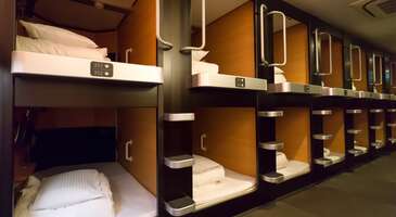 Seyahat alışkanlıkları değiştik&ccedil;e konaklama se&ccedil;enekleri de gelişiyor. Kaps&uuml;l oteller gezginlere, l&uuml;ks otellerin sunduğu geniş odalar veya hostellerin paylaşımlı ranzaları yerine başka bir alternatif sunuyor. Giderek pop&uuml;lerlik kazanan kaps&uuml;l oteller, minimalist, teknolojik ve b&uuml;t&ccedil;e dostu bir se&ccedil;enek olarak y&uuml;kseliyor.&nbsp; Son yıllarda adı sık&ccedil;a duyulan kaps&uuml;l otel konsepti, tam olarak nedir ve kimler i&ccedil;in uygun? Bir gezginin kaps&uuml;l oteller hakkında bilmesi gereken her şeye birlikte g&ouml;z atalım. Kaps&uuml;l otel&nbsp; Kaps&uuml;l otel, misafirlerin sadece uyuması ve dinlenmesi amacıyla tasarlanmış, "kaps&uuml;l" adı verilen k&uuml;&ccedil;&uuml;k, mod&uuml;ler &uuml;nitelerde konaklama şansı sunan bir otel t&uuml;r&uuml;. Kaps&uuml;l otellerde, geleneksel otel odalarında bulunan &ccedil;alışma masası, koltuk veya geniş alanların yerini sadece bir yatak b&uuml;y&uuml;kl&uuml;ğ&uuml;ndeki y&uuml;ksek teknolojili kabin alıyor. Bu konseptin temel felsefesi ise maksimum verimlilik ve minimum maliyet &uuml;zerine kurulu. Kaps&uuml;l oteller, gezginlere bir şehirde sadece uyumak i&ccedil;in ihtiya&ccedil; duydukları kadar alan sunarak, gereksiz oda masraflarından tasarruf etmelerini sağlıyor. Kaps&uuml;l otellerin tarih&ccedil;esi Kaps&uuml;l otel fikri, ilk kez 1979 yılında Japonya&rsquo;nın Osaka şehrinde doğdu. &Uuml;nl&uuml; mimar Kisho Kurokawa tarafından tasarlanan "Capsule Inn Osaka", d&uuml;nyanın ilk kaps&uuml;l oteli olarak tarihe ge&ccedil;ti. Başlangı&ccedil;ta iş &ccedil;ıkışı son treni ka&ccedil;ıran veya uygun fiyatlı bir geceleme mek&acirc;nı arayan iş insanları i&ccedil;in tasarlanan bu konsept, zamanla d&uuml;nya genelindeki sırt &ccedil;antalı gezginlerin ve minimalist yaşamı sevenlerin g&ouml;zdesi haline geldi. Kaps&uuml;l otelde konaklama deneyimi Kaps&uuml;l otellerde s&uuml;re&ccedil;, standart bir otele g&ouml;re biraz farklı ama olduk&ccedil;a sistematik işliyor. Giriş ve dolaplar: &Ouml;zellikle Japonya&rsquo;daki kaps&uuml;l otellerde ayakkabılarını dışarıdaki dolaplara bırakabilir ve sana verilen terlikleri giyebilirsin. Valizlerin ve kişisel eşyaların i&ccedil;in sana &ouml;zel tahsis edilen kilitli b&uuml;y&uuml;k dolapları (locker) kullanabilirsin. Kaps&uuml;l&uuml;n i&ccedil;i: Kaps&uuml;l&uuml;n i&ccedil;ine girdiğinde seni konforlu bir yatak, ayarlanabilir ışıklandırma, havalandırma, elektrik prizleri, Wi-Fi ve bazen de k&uuml;&ccedil;&uuml;k bir televizyon karşılıyor. Kaps&uuml;l&uuml;n ağzı bir perde veya s&uuml;rg&uuml;l&uuml; kapı ile kapatılarak kişisel mahremiyet sağlanıyor. Ortak alanlar: Banyo, tuvalet ve dinlenme salonları genellikle ortak kullanılıyor. Ancak modern kaps&uuml;l otellerde bu alanlar olduk&ccedil;a l&uuml;ks, hijyenik ve modern tasarımlara sahip. {insightBoxStart}İpucu: En iyi otel fiyatlarını tek bir yerde g&ouml;rmek, se&ccedil;eceğin otel hakkında bilgi almak ve saniyeler i&ccedil;inde rezervasyon yapmak i&ccedil;in ENUYGUN'da otel araştırmasına başlayabilirsin.{insightBoxEnd} {hotel_search_form_banner} Kaps&uuml;l otellerin avantajları ve dezavantajları Her konaklama t&uuml;r&uuml;nde olduğu gibi kaps&uuml;l otellerin de kendine &ouml;zg&uuml; artıları ve eksileri bulunuyor. Kaps&uuml;l otel avantajları: Ekonomik: Kaps&uuml;l otel, standart bir otel odasına g&ouml;re &ccedil;ok daha uygun fiyatlı. Konum: Kaps&uuml;l oteller, &ccedil;oğunlukla şehir merkezlerinde, tren istasyonlarına veya havaalanlarına y&uuml;r&uuml;me mesafesinde bulunuyor. Yeni bir deneyim: Uzay &ccedil;ağını andıran f&uuml;t&uuml;ristik tasarımıyla kaps&uuml;l oteller, sıra dışı bir konaklama deneyimi yaşatıyor. Hijyen: Modern kaps&uuml;l otellerde temizlik standartları sıkı olabiliyor. Ayrıca minimal eşya kullanımı da ortamın daha steril olmasını sağlıyor. Kaps&uuml;l otel dezavantajları: Dar alan: Klostrofobisi (kapalı alan korkusu) olanlar i&ccedil;in kaps&uuml;l otel, &ccedil;ok uygun olmayabilir. Ses izolasyonu: Kaps&uuml;ller, genellikle ince malzemeden yapıldığı i&ccedil;in yan kabindeki horlama veya hareket seslerini duyma ihtimali var. Sınırlı hareket alanı: Kıyafet değiştirmek veya valiz a&ccedil;mak gibi işlemlerin ortak alanlardaki dolapların başında yapılması bazı zorluklar &ccedil;ıkarabiliyor. Kaps&uuml;l oteller kimler i&ccedil;in uygun? Kaps&uuml;l oteller, b&uuml;t&ccedil;esini konaklama yerine gezmeye ayırmak isteyenler, tek başına seyahat edenler, u&ccedil;uşları arasında uzun bekleme s&uuml;resi olan transit yolcular ve minimalist seyahati seven teknoloji meraklıları i&ccedil;in g&uuml;zel bir tercih. &Ouml;zellikle Japonya, İzlanda ve Singapur gibi konaklamanın pahalı olduğu &uuml;lkelerde kaps&uuml;l otel, hayat kurtarıcı olabiliyor. Rezervasyon yapabileceğin kaps&uuml;l oteller: Attic Capsule Hotel (Cebu Adası, Lapu-Lapu) Capsule Inn Medan (Medan) OOstel Smart Capsule Hostel (Riviera Maya, Tulum) Vintage Inn Boutique Capsule (Singapore) Shinjuku Sky Capsule (Tokyo) Full House Capsule Hostel (Rivne - Batı Ukrayna) Capsule Hotel Wellbe Sakae (&Ccedil;ubu, Nagoya) Capsule hotel ALOHA (Vladivostok) Buran Capsule Hotel (Moskova) DONGMEN 3 Capsule Inn - Hostel (Taipei) InBox Capsule Hotel (St. Petersburg) Capsule Hotel Anshin Oyado Premier Kyoto Shijo Karasuma (Kyoto) Kapsuła Hostel Warszawa (Varşova) Kabin Kapsul Kayu Jati V - Hostel (Jakarta) Kabin Kapsule UI Depok (Jakarta) {insightBoxStart}Yazar Notu: İstanbul Havalimanı dahil d&uuml;nyanın bazı b&uuml;y&uuml;k havalimanlarında bu kaps&uuml;lleri (uyku kabinlerini) saatlik olarak kiralayıp deneyebilirsin.{insightBoxEnd} Tatil planı yaparken doğru oteli se&ccedil;mekte zorlanıyorsan hedef kitlesine g&ouml;re otel se&ccedil;imi yazımızı inceleyebilirsin.