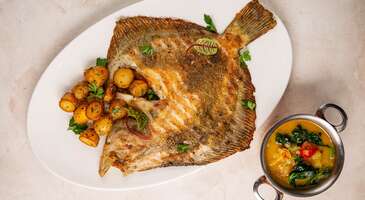 Yeni bir şehri ziyaret ettiğinde ilk &ouml;ğ&uuml;n kafanı karıştırabilir. Ama merak etme, Varna'nın sokaklarında &ccedil;ocukluğundan kalma tanıdık bir kokuyla karşılaşacaksın. Varna'da sofraya oturduğunda, ismini telaffuz edemediğin o yemeği yediğin ilk anda "Aa, bu tadı biliyorum!" diyeceksin. Bulgaristan&rsquo;ın deniz başkenti olarak bilinen Varna, Balkan geleneklerini deniz esintisiyle harmanlandığı zengin mutfağıyla da etkileyici bir şehir. Osmanlı d&ouml;nemi izleri taşıyan baharatlı et yemeklerinden Karadeniz&rsquo;in en taze balıklarına, iştah a&ccedil;ıcı mezelerden asil tatlılara kadar Varna gastronomisi, tam bir k&uuml;lt&uuml;rel kavşak noktası.&nbsp; Varna&rsquo;nın sahil şeridindeki şık restoranlardan şehrin dar sokaklarına gizlenmiş otantik meyhanelere kadar her k&ouml;şe başında seni farklı bir lezzet ser&uuml;veni bekliyor. Yerel malzemelerin doğallığı ve Balkan mutfağının misafirperverliği, Varna seyahatini unutulmaz bir lezzet ş&ouml;lenine d&ouml;n&uuml;şt&uuml;rebilir.&nbsp; 1. Varna usul&uuml; midye Varna&rsquo;nın denizci ruhunu ve Karadeniz&rsquo;in c&ouml;mertliğini aynı tabakta buluşturan Varna usul&uuml; midye, şehrin gastronomi kimliğinin en karakteristik par&ccedil;ası. Alışılagelmiş midye dolmaların aksine bu lezzet, genellikle taze toplanmış midyelerin pirin&ccedil;, soğan, domates ve bolca taze dereotu ile bir tencere yemeği kıvamında yavaş&ccedil;a pişirilmesi ile hazırlanıyor. Bu yemek, Karadeniz&rsquo;in iyot kokusunu pirincin doyuruculuğu ve baharatların aroması ile birleştiriyor. Salaş balık&ccedil;ı lokantalarında veya sahil şeridindeki şık restoranlarda tadabileceğin Varna usul&uuml; midye, bir kadeh soğuk Bulgar beyaz şarabı ile servis ediliyor.&nbsp; 2. Tarator (Soğuk yoğurt &ccedil;orbası) Sıcak yaz g&uuml;nlerinde Varna&rsquo;nın en sevilen ferahlık kaynağı olan tarator, hem bir &ccedil;orba hem de iştah a&ccedil;ıcı bir meze. Yoğurdun suyla inceltilmesi ile hazırlanan bu soğuk lezzetin i&ccedil;ine katılan ince kıyılmış &ccedil;ıtır salatalık, sarımsak ve bolca taze dereotu, damakta tatlı bir serinlik bırakıyor. Taratoru sıradan bir yoğurt karışımından ayıran asıl dokunuş ise &uuml;zerine serpilen d&ouml;v&uuml;lm&uuml;ş ceviz i&ccedil;i ve birka&ccedil; damla kaliteli yağ (genellikle ay&ccedil;i&ccedil;ek yağı). Bu k&uuml;&ccedil;&uuml;k detaylar, yemeğe gurme bir derinlik ve karakteristik bir Balkan karakteri ekliyor. Tarator, Varna&rsquo;nın deniz manzaralı restoranlarında ana yemek &ouml;ncesi kasede veya bardakta sunuluyor. Bu ferahlatıcı karışım, Karadeniz g&uuml;neşinin altındaki en lezzetli ka&ccedil;amaklardan biri. 3. Kavarma Varna mutfağının geleneksel ana yemeklerinden olan kavarma, Balkanların bereketini yansıtan bir toprak kap (gyuveche) ziyafeti. Bu lezzet, kuşbaşı doğranmış etlerin (genellikle dana veya tavuk), bol soğan, mantar, k&ouml;zlenmiş biber ve domates sosuyla buluşması ile hazırlanıyor. Yemeğin fırında ağır ağır pişirilmesi, t&uuml;m aromaların birbirine ge&ccedil;mesini sağlıyor. Kavarmanın en karakteristik &ouml;zelliği ise fırından &ccedil;ıkmadan hemen &ouml;nce &uuml;zerine kırılan ve sarısı hafif akışkan bırakılan yumurtası. Bu dokunuş, yemeğe g&ouml;rsel bir imza ve &ouml;zel bir doku katıyor. Varna&rsquo;nın otantik restoranlarında, kapağı a&ccedil;ıldığında y&uuml;kselen o iştah a&ccedil;ıcı dumanı ile servis edilen kavarma, serin akşamlarda i&ccedil;ini ısıtacak bir tercih. 4. Kalkan ızgara (Grilled turbot) Karadeniz&rsquo;in en se&ccedil;kin balığı kabul edilen kalkan, Varna&rsquo;nın denizci mutfak k&uuml;lt&uuml;r&uuml;n&uuml;n zirve noktalarından biri. Karadeniz&rsquo;de "balıkların kralı" olarak bilinen kalkan, beyaz ve yağlı eti ile gurmeler i&ccedil;in vazge&ccedil;ilmez bir lezzet. Kalkan ızgara, Varna&rsquo;nın sahil restoranlarında genellikle sadece zeytinyağı, kaya tuzu ve taze limonla marine edilerek odun ateşinde veya ızgarada pişiriliyor. Bu balık, dışının hafif &ccedil;ıtırlığına karşın i&ccedil;indeki sulu ve yumuşak dokusunu &ouml;zel bir şekilde koruyor. Kalkan ızgara, genellikle yanında k&ouml;zlenmiş sebzeler veya taze otlarla harmanlanmış patatesler ile servis ediliyor. {insightBoxStart}İpucu: Varna'da uyanacağın o g&uuml;zel sabahlar i&ccedil;in odan şimdiden hazır bile. En iyi otel fiyatlarını tek bir yerde g&ouml;rmek, se&ccedil;eceğin otel hakkında bilgi almak ve saniyeler i&ccedil;inde rezervasyon yapmak i&ccedil;in ENUYGUN'da Varna otelleri araştırmasına başlayabilirsin.{insightBoxEnd} {hotel_search_form_banner} 5. Banitsa (Peynirli Bulgar b&ouml;reği) Varna&rsquo;nın sabah enerjisini simgeleyen en k&ouml;kl&uuml; hamur işi ise banitsa. Bu lezzetli b&ouml;rek, Varna fırınlarından y&uuml;kselen karşı konulmaz tereyağı kokusunun ana kaynağı. Banitsa hazırlanırken incecik a&ccedil;ılmış el yapımı yufkaların arasına yumurta, yoğurt ve Bulgaristan&rsquo;ın meşhur beyaz peyniri (sirene) ile hazırlanan zengin bir har&ccedil; konuluyor. Daha sonra ise yufkalar rulo yapılıyor. B&ouml;rek, fırında altın sarısı bir renk alana kadar pişiriliyor. Sabahın erken saatlerinde fırından gelen mis gibi peynir ve maya kokusunu i&ccedil;ine &ccedil;ektiğini hayal et. Dışı &ccedil;ıtır &ccedil;ıtır, i&ccedil;i ise kat kat ve yumuşak olan banitsa, Varna&rsquo;da g&uuml;n&uuml;n her saatinde keyifle t&uuml;ketilen mill&icirc; bir gurur. Varna&rsquo;nın kafelerinde de bulabileceğin banitsa, yanında buz gibi bir bardak ayran veya geleneksel bir kadeh boza ile servis ediliyor.&nbsp; 6. Kebapche ve kyufte (Izgara Balkan etleri) Kebapche ve kyufte, Balkan mutfağında ızgara k&uuml;lt&uuml;r&uuml;n&uuml; temsil eden &ouml;zel lezzetler. Bu et yemekleri, Varna&rsquo;nın l&uuml;ks restoranlarında ve samimi sokak lezzet duraklarında karşına &ccedil;ıkacak. Kebapche, parmak şeklinde uzun ve genellikle kimyonla harmanlanmış bir t&uuml;r k&ouml;fte. Kyufte ise i&ccedil;ine bazen ince kıyılmış soğan ve "chubritza" denilen dağ kekiği eklenen daha yassı ve dolgun bir lezzet. Her iki ızgara da k&ouml;m&uuml;r ateşinde dışı m&uuml;h&uuml;rlenip i&ccedil;i sulu kalacak şekilde pişirildiğinde Balkan etlerinin o kendine has isli ve yoğun aromasını kazanıyor. Bu ikili, Varna&rsquo;da geleneksel olarak yanında fırınlanmış patates, k&ouml;zlenmiş biber ve meşhur domates-biber sosu olan "lyutenitsa" ile servis ediliyor. 7. Şopska salata (Shopska salad) Bulgar mutfağının tartışmasız krali&ccedil;esi olan şopska salata, Varna sofralarının da en renkli başlangıcı. Bu &ouml;zel salata, sadeliğin lezzetle buluştuğu bir gastronomi klasiği. Şopska salata, geleneksel olarak kırmızı domates, &ccedil;ıtır salatalık, k&ouml;zlenmiş biber, soğan ve ince kıyılmış maydanozlar ile hazırlanıyor. Bu karışım, &uuml;zerine kar taneleri gibi bolca rendelenen meşhur "sirene" peyniri ile birleştiğinde ise ortaya g&ouml;rsel bir ş&ouml;len &ccedil;ıkıyor. Salatanın &uuml;zerine kar gibi rendelenen o sert beyaz peynirin, mis gibi domatesle birleştiği an, yediğin bu lezzeti asla unutamayacaksın. Renkleriyle Bulgar bayrağını simgeleyen şopska salata, sadece bir salata değil, Karadeniz manzaralı akşam yemeklerinin ve buz gibi bir kadeh i&ccedil;kinin en g&uuml;zel eşlik&ccedil;isi. 8. Garash pasta (Garaş pastası) Bulgaristan&rsquo;ın d&uuml;nya gastronomisine kazandırdığı en şık ve aristokrat tatlı olan garash pasta, Varna&rsquo;nın k&ouml;kl&uuml; pastanelerinde tadabileceğin eşsiz bir &ccedil;ikolata başyapıtı. 19. y&uuml;zyılın sonlarında yaratılan bu ikonik tatlının en ayırt edici &ouml;zelliği ise hamurunda neredeyse hi&ccedil; un kullanılmaması. Katmanlar sadece d&ouml;v&uuml;lm&uuml;ş ceviz ve yumurta akından oluşan ince, kıtır mereng dokulu keklerden oluşuyor. Bu narin katmanların arasına ve &uuml;zerine s&uuml;r&uuml;len yoğun bitter &ccedil;ikolatalı krema (ganaj), pastaya kadifemsi bir zenginlik katıyor. Bu lezzetli tatlı, &ouml;zellikle cevizin aromasıyla kusursuz bir uyum yakalıyor. Garash pasta, Varna&rsquo;nın otantik atmosferini hissettirecek, ağır ama bir o kadar asil bir tatlı. 9. S&uuml;tl&uuml; banitsa (Mlechna banitsa) S&uuml;tl&uuml; banitsa, Bulgaristan&rsquo;ın en sevilen hamur işi olan banitsanın benzersiz bir tatlıya d&ouml;n&uuml;şt&uuml;ğ&uuml; farklı bir lezzet. Bu banitsa &ccedil;eşidi, Varna&rsquo;da bir kahvaltı klasiği ve hafif bir tatlı olarak &ouml;zel bir yere sahip. S&uuml;tl&uuml; banista, incecik yufkaların fırında hafif&ccedil;e kurutulmasının ardından &uuml;zerine s&uuml;t, yumurta, şeker ve vanilyadan oluşan zengin bir karışımın d&ouml;k&uuml;l&uuml;p yeniden pişirilmesi ile hazırlanıyor. Bu lezzet, dokusu ile fırın s&uuml;tla&ccedil; ile yumuşak bir b&ouml;rek arasında gidip geliyor. S&uuml;tl&uuml; banitsa, yufka katmanlarının s&uuml;t&uuml; tamamen &ccedil;ekerek bulutsu bir kıvam almasıyla da &uuml;nl&uuml;. Varna&rsquo;nın yerel kafelerinde hem ılık hem de soğuk olarak servis edilen s&uuml;sl&uuml; banitsa, Balkanlar&rsquo;ın m&uuml;tevazı malzemelerle yarattığı ustalığın bir temsilcisi. 10. Kabaklı banitsa (Tikvenik) Sonbahar ve kış aylarında Varna sokaklarını saran tar&ccedil;ın kokusunun kahramanı ise kabaklı banitsa. Bu banitsa &ccedil;eşidi, Balkanlar&rsquo;ın doğa ile barışık mutfak k&uuml;lt&uuml;r&uuml;n&uuml; yansıtan en &ouml;zg&uuml;n tatlılardan biri. Kabaklı banitsa, rendelenmiş bal kabağının toz şeker, bolca d&ouml;v&uuml;lm&uuml;ş ceviz ve tar&ccedil;ınla harmanlanıp incecik yufkalara sarılması ile hazırlanıyor. Yufkalar, fırında altın sarısı bir &ccedil;ıtırlığa ulaşana dek pişiriliyor. Banitsanın dışındaki o gevrek katmanların arasından gelen yumuşak ve aromatik kabak dolgusu, her lokmada sıcak bir huzur veriyor. Genellikle &uuml;zerine pudra şekeri serpilerek servis edilen kabaklı banitsa, Varna&rsquo;nın serin deniz havasında i&ccedil;ini ısıtacak hafif ve geleneksel bir final tercihi. {{campaignsSlider}} 11. Rakia (Bulgar rakısı) Rakia, Bulgaristan&rsquo;ın mill&icirc; i&ccedil;eceği ve Varna sofralarının vazge&ccedil;ilmez temel taşı. Rakia, meyvenin saflığını ve karakterini yansıtan olduk&ccedil;a g&uuml;&ccedil;l&uuml; bir damıtma sistemiyle hazırlanıyor. Genellikle &uuml;z&uuml;m veya erikten bazen de kayısı gibi b&ouml;lgenin bereketli meyvelerinden &uuml;retilen i&ccedil;ecek, sadece bir alkol değil, Balkan misafirperverliğinin simgesi. Rakia, Varna&rsquo;nın yerel meyhanelerinde bir rit&uuml;el olarak da sunuluyor. D&uuml;nyadaki diğer &ouml;rneklerinin aksine rakia, yemeğin sonunda değil, başında ve mutlaka taze bir şopska salata eşliğinde yavaş yavaş yudumlanıyor. Meyvenin doğal aromasını kokusunda ve tadında yoğun olarak hissettiren rakia, boğazdan ge&ccedil;erken ise sıcak bir iz bırakıyor. 12. Euxinograd şarapları ve konyakları Varna&rsquo;nın kuzey kıyısındaki Euxinograd Sarayı, sadece mimarisi ile değil, Bulgaristan&rsquo;ın en se&ccedil;kin bağcılık geleneklerine ev sahipliği yapmasıyla da &uuml;nl&uuml;. Saray, gastronomi d&uuml;nyasında &ouml;zel bir yere sahip. Karadeniz&rsquo;in nemli ve yumuşak mikrokliması ile beslenen saray bağlarında &uuml;retilen Euxinograd şarapları, &ouml;zellikle &ldquo;chardonnay&rdquo; ve &ldquo;traminer&rdquo; gibi beyaz &uuml;z&uuml;m &ccedil;eşitlerinin sunduğu aromalarıyla &uuml;nl&uuml;. Bu k&ouml;kl&uuml; geleneğin en prestijli par&ccedil;ası ise Fransız "charentes" y&ouml;ntemine sadık kalınarak meşe fı&ccedil;ılarda yıllandırılan ve sofistike bir i&ccedil;im sunan Euxinograd konyakları. Varna seyahatinde sarayın asırlık mahzenlerinden &ccedil;ıkan bu i&ccedil;ecekleri deneyerek, Karadeniz&rsquo;in yerel dokusunu Avrupa&rsquo;nın saray mutfağı zarafeti ile harmanlayabilirsin. 13. Oblak (Bulut) kokteyli Varna&rsquo;nın sıcak yaz akşamlarında serinlemenin en g&uuml;zel yolu, anasonun ferahlatıcı g&uuml;c&uuml;n&uuml; temsil eden mastika ile hazırlanan oblak kokteyli. Bulgaristan&rsquo;ın geleneksel anason aromalı sert bir i&ccedil;kisi olan mastika, tek başına buz gibi servis edildiğinde kristalleşen yapısı ile &uuml;nl&uuml;. Ancak Varna&rsquo;ya &ouml;zg&uuml; asıl deneyim, bu i&ccedil;kinin naneli yeşil lik&ouml;r olan menta ile karıştırılması. Bardakta bir araya geldiklerinde ortaya &ccedil;ıkan puslu ve bulutsu g&ouml;r&uuml;nt&uuml;den adını alan bu kokteyl, anasonun keskinliği ile nanenin serinliğini birleştiriyor. Karadeniz&rsquo;in sahil havasında, buz gibi soğuk yudumlanan oblak kokteyli, Varna&rsquo;nın rahat ruhunu yansıtan en pop&uuml;ler yerel i&ccedil;eceklerden biri. Birbirinden lezzetli bu yemekleri yerinde denemek istersen Bulgaristan&rsquo;da gezilecek yerler yazımızı inceleyebilirsin.