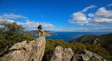 National Geographic Traveller Birleşik Krallık, 2021&rsquo;de gezilecek en iyi 35 yerin listesini yaptı. 5 ayrı başlık altında toplanan yerler arasına bu sene T&uuml;rkiye&rsquo;den antik Karia Yolu dahil oldu. Macera kategorisindeki rota, T&uuml;rkiye&rsquo;nin en uzun y&uuml;r&uuml;y&uuml;ş yolu. Senin i&ccedil;in bu yola dair her şeyi tek yazıya topladım. Antik Karia Yolu nerede? Bozburun Yarımadası, Dat&ccedil;a, G&ouml;kova K&ouml;rfezi, İ&ccedil; Karia ve Muğla &ccedil;evresinden oluşan yol 850 km uzunluğunda. 4 ana ve 1 ek b&ouml;l&uuml;mden oluşan rotayı y&uuml;r&uuml;mek i&ccedil;in herhangi bir noktasından başlayabilirsin. Hem Akdeniz hem Ege b&ouml;lgelerinde yer alan yol &ccedil;eşitli zorluklar barındırsa da manzara t&uuml;m zorluklara değiyor. {flight_search_form_banner} Bu yol nasıl bulundu? Altay &Ouml;zcan liderliğinde Yunus &Ouml;zdemir, Dean Livesley ve Volkan Demir 2009 yılında y&uuml;r&uuml;yerek Karia Yolu'nu keşfettiler. Bu ekip ayrıca yol &uuml;zerindeki ilk işaretlemeleri de yaptı. Altay &Ouml;zcan'ın Karia Yolu hakkında iki rehber kitabı bulunuyor. Buraya yolculuğa &ccedil;ıkacaklara bu kitapları almalarını &ouml;neririz. Ayrıca Altay &Ouml;zcan, her yıl rota &uuml;zerinde patika temizliği ve levha d&uuml;zenlemeleri gibi &ccedil;alışmalar y&uuml;r&uuml;t&uuml;yor. 2013 yılında resmi olarak a&ccedil;ılan Karia Yolu olup eşsiz bir deneyim vadediyor. Karia Yolu neden tarihi bir rota? Antik Karia (Karya) Uygarlığı'ndan ismini alan Karia Yolu rotasında, M.&Ouml;. 7000 yılına kadar uzanan kalıntılara rastlamak m&uuml;mk&uuml;n. Bu rota &uuml;zerinde Knidos'tan Amos'a, Halikarnassos'tan Alinda'ya kadar bir&ccedil;ok bilinen antik şehir ve isimsiz harabe yerleri yer alıyor. Karia Yolu, Likya Yolu'na alternatif olarak g&ouml;sterilebilir. Likya Yolu ile ilgili okuma yapmak istersen Likya Yolu Seyahati İ&ccedil;in Sorabileceğin 12 Soru ve Cevapları yazımıza da bakabilirsin. Bu yol tek seferde y&uuml;r&uuml;n&uuml;r m&uuml;? Hem uzunluğu hem de zorlu parkurları sebebiyle bu yol tek seferde y&uuml;r&uuml;nemiyor. Sana tavsiyem her b&ouml;l&uuml;m i&ccedil;in bir zaman dilimi ayırıp y&uuml;r&uuml;y&uuml;ş&uuml;n tadını &ccedil;ıkarman. Rota &uuml;zerinde bisiklet ve kano gibi doğa sporlarını da yapabilirsin.&nbsp; Rotanın parkurları neler? Toplam 5 b&ouml;l&uuml;me sahip Karia Yolu&rsquo;nda 46 etap bulunuyor. Gel bakalım bu etaplar nerelerden ge&ccedil;iyor&hellip; Bozburun Yarımadası:İ&ccedil;meler'den başlayıp Hisar&ouml;n&uuml;'nde sonlanan 145 km uzunluğundaki yol, yarımadayı sahil boyunca takip ediyor. Turistik kalabalıktan uzak ve ulaşımın zor olmasıyla sakinlik sevenler i&ccedil;in ideal. Dat&ccedil;a Yarımadası:&nbsp;Eski Dat&ccedil;a'dan başlayıp Knidos Antik Kenti'ne ulaşan bu b&ouml;l&uuml;m, rotadaki favori kısımlardan. Knidos, Akdeniz ve Ege Denizi'nin birleştiği noktada yer alan &ouml;nemli bir antik kent. Knidos'tan sonra rota yarımadanın &uuml;st kıyısından i&ccedil;eri doğru ilerler ve Akyaka'da son bulur. G&ouml;kova K&ouml;rfezi: Enfes k&ouml;rfez manzaraları, denize girmelik ıssız koylar ve kıvrımlı yollara sahip bu b&ouml;l&uuml;mde diğerlerine nazaran daha az sayıda etap bulunuyor. Akyaka&rsquo;da başlayan rota, yine sahil şeridini takip ederek Bodrum&rsquo;a ulaşıyor. İ&ccedil; Karia:&nbsp;Muhteşem k&ouml;rfez manzaraları, ıssız koylar ve kıvrımlı yolların olduğu bu b&ouml;l&uuml;mde diğerlerine g&ouml;re daha az sayıda etap bulunur. Akyaka'dan başlayıp Bodrum'a kadar sahil boyunca ilerler. Muğla ve &Ccedil;evresi:&nbsp;Akyaka'dan başlayarak eski bir kervan yolunu izler. Bozburun Yarımadası'na benzer g&uuml;zergahlara sahip olan bu yol, eski Muğla şehrinden ge&ccedil;er. Karia Yolu&rsquo;na nasıl giderim? Eğer Bozburun Yarımadası&rsquo;nı y&uuml;r&uuml;meyi planlıyorsan İ&ccedil;meler&rsquo;den yola &ccedil;ıkabilirsin. Marmaris&rsquo;in bu şirin beldesine ulaşmak i&ccedil;in Dalaman u&ccedil;ak bileti&nbsp;alarak transfer ya da toplu taşıma ile Marmaris&rsquo;e ulaşabilirsin. Dat&ccedil;a Yarımadası b&ouml;l&uuml;m&uuml;n&uuml; y&uuml;r&uuml;yeceksen y&uuml;r&uuml;y&uuml;şe başlamadan &ouml;nce bir iki g&uuml;n Dat&ccedil;a otellerinde konaklayarak bu şirin il&ccedil;enin tadını &ccedil;ıkarmanı &ouml;neririm. Dilersen rotaya Akyaka tarafından başlayarak Eski Dat&ccedil;a&rsquo;da da bitirebilirsin. G&ouml;kova K&ouml;rfezi b&ouml;l&uuml;m&uuml;n&uuml;yse ister Bodrum ister Akyaka&rsquo;ya ulaşarak y&uuml;r&uuml;men m&uuml;mk&uuml;n. Başlangı&ccedil; i&ccedil;in doğru bir nokta yok. Burada se&ccedil;im tamamen sana kalıyor kısacası. Her iki yere de bir otob&uuml;s bileti uzaklığındasın! İ&ccedil; Karia b&ouml;l&uuml;m&uuml; ulaşım i&ccedil;in en zorlayıcı olabilecek kısım. Bozalan&rsquo;dan başlayıp Karpuzlu&rsquo;da biten yolda y&uuml;r&uuml;mek i&ccedil;in Muğla Belediyesi&rsquo;nin şehir i&ccedil;i ulaşımına bakabilirsin. D&ouml;nem d&ouml;nem değişen seferlerin y&ouml;nleri ve saatleri i&ccedil;in yol planı yaparken kontrol etmeni &ouml;neririm. Y&uuml;r&uuml;y&uuml;ş &ouml;ncesi tavsiyeleri neler? Sınırlarını bilmek i&ccedil;in &ouml;nce şehir i&ccedil;inde y&uuml;r&uuml;y&uuml;ş yaparak deneyim kazanabilirsin. Evine yakın y&uuml;r&uuml;y&uuml;ş parkurlarında veya ormanlık alanlarda test yaparak g&uuml;nl&uuml;k kilometre sınırını &ouml;ğrenebilirsin. Rahat ayakkabı ve nefes alabilen kıyafetler alışveriş listesinde olmalı. Yolculukta beraber olmayı d&uuml;ş&uuml;nd&uuml;ğ&uuml;n kişilerle daha &ouml;nce kısa bir tatil yaparak birbirinizi daha iyi tanıyabilirsin. Planlamayı iyi yap, konaklama ve market gibi ihtiya&ccedil;lar i&ccedil;in işaretlemeler yap. GPS cihazı veya cep telefonunu kullanabilirsin. Konaklamayı nerelerde yapabilirim? Karia Yolu &uuml;zerinde kamp atabileceğin pek &ccedil;ok nokta bulunuyor. Hem kamp alanlarında hem yol &uuml;zerinde bir tesise bağlı olmaksızın &ccedil;adır kurabilirsin. Tabii ki kamp alanları ve diğer konaklama se&ccedil;enekleri duş, elektrik gibi ihtiya&ccedil;larını karşılaman i&ccedil;in &ccedil;ok daha iyi oluyor. Etap etap y&uuml;r&uuml;yeceğin i&ccedil;in konaklama alanlarını işaretleyerek g&uuml;nl&uuml;k y&uuml;r&uuml;y&uuml;ş miktarını belirleyebilirsin. Tek başıma y&uuml;r&uuml;yebilir miyim? Uzun ve zorlu parkurlarda tek başına trekking yapmak pek akıllıca olmuyor. Oluşabilecek acil durumlarda yanında en az bir kişinin olması &ouml;nemli. &Uuml;stelik yalnızlığı sevsen bile bazı işler i&ccedil;in birden &ccedil;ok kişi gerekebiliyor. Bu sebeplerle Karia Yolu&rsquo;nu tek başına y&uuml;r&uuml;meni tavsiye etmiyorum. Ancak tek başına y&uuml;r&uuml;meye kararlıysan ve ilk trekking yapışın değilse rotanı bir yakınına haber vermeli ve konumunu sıklıkla g&uuml;ncellemelisin. Bu yolu ne zaman y&uuml;r&uuml;yebilirim? Akdeniz iklimi etkisinde bulunan b&ouml;lgede y&uuml;r&uuml;y&uuml;ş&uuml;n&uuml; zorlaştıracak tek mevsim yaz! Sıcak ve nem hem y&uuml;r&uuml;y&uuml;ş hızını yavaşlatabilir hem de daha &ccedil;ok su ihtiyacı duyabilirsin. G&uuml;neş &ccedil;arpmaları ise tuzu biberi olur. Benim &ouml;nerim ilkbahar ayları olacak. Ancak kışın bile gitsen kar g&ouml;rmenin &ccedil;ok zor olduğu bir rota burası. Bu y&uuml;zden hangi zamanı se&ccedil;ersen se&ccedil;, &ouml;nemli olan malzemelerini buna g&ouml;re hazırlaman. Tabii yağmurda trekking yapmanın sevimsizliğini hatırlarsan bahar ayları ile ciddi d&uuml;ş&uuml;n derim. Y&uuml;r&uuml;y&uuml;ş sırasında nelere dikkat etmeli? Engebeli arazide dikkatli y&uuml;r&uuml;melisin ve baton kullanman faydalı olabilir. Su, yiyecek ve ilkyardım &ccedil;antasını yanında bulundurmalısın. Bazı etaplarda su bulmak zor olabilir, bu y&uuml;zden suyunu &ouml;nceden temin etmelisin. Alışverişlerini yol &uuml;zerindeki yerleşim yerlerinden yapabilirsin. &Ccedil;adır kuracaksan uygun bir alan se&ccedil;melisin. Ateş yakmak i&ccedil;in izin verilmeyen bir alandasın, bu y&uuml;zden ateşi unutmalısın. Doğal yaşam alanında olduğun i&ccedil;in hayvanlar i&ccedil;in &ouml;nlem almalısın ve &ccedil;&ouml;plerini toplamalısın. Rotada y&uuml;r&uuml;rken iz bırakmak istersen sadece ayak izin olsun. İşaretlemelere dokunmamaya &ouml;zen g&ouml;stermelisin. Doğal yaşamı korumak i&ccedil;in ses kirliliğinden ka&ccedil;ınmalısın.
