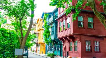 İstanbul&rsquo;un eski semtleri denilince ilk akla gelen yerdir Kuzguncuk. Samimi ve sıcak atmosferi sayesinde hayran olacağın, tarihe ışık tutan yapıları yanında&nbsp; g&uuml;n&uuml;m&uuml;zde mahalle k&uuml;lt&uuml;r&uuml;n&uuml;n hala yaşadığı yer olması ile mutlaka kendinden bir şey bulabileceğin, rengarenk cumbalı evleri, organik &uuml;r&uuml;nleri satın alabileceğin bostanı, arnavut kaldırımlı daracık sokakları, &ccedil;i&ccedil;ekli pencere &ouml;nleri, nostaljik havası eşliğinde kahveni i&ccedil;ip, kitabını okuyabileceğin tatlı kafeleri ile İstanbul&rsquo;da Gezilecek yerler arasında bulunan &Uuml;sk&uuml;dar Kuzguncuk&rsquo;u benimle keşfetmeye ne dersin? Kuzguncuk nerede? Kuzguncuk Boğazi&ccedil;i&rsquo;nin Anadolu kıyısında, &Uuml;sk&uuml;dar il&ccedil;esine bağlı eski ve tatlı bir yerleşim yeri. Kadık&ouml;y&rsquo;e 11 km, Beylerbeyi&rsquo;ne 2 km, Boğazi&ccedil;i K&ouml;pr&uuml;s&uuml;ne ise 3 km mesafede bulunuyor. Kuzguncuk'un tarihi Kuzguncuk&rsquo;u gezerken bir k&ouml;şede cami, diğer k&ouml;şede sinagog, başka bir k&ouml;şede bir kilise g&ouml;rmen pek m&uuml;mk&uuml;n. Kuzguncuk&rsquo;un yerleşim tarihi olduk&ccedil;a eskilere dayanıyor. Evliya &Ccedil;elebi&rsquo;ye g&ouml;re Kuzguncuk adını d&ouml;nemin meşhur dervişlerinden olan ve burada yaşayan Kuzgun Baba&rsquo;dan almış. Bizans d&ouml;nemine&nbsp; dayanan yerleşimi sebebiyle semtin eski adının Hrisokeramos olduğu yani &ldquo;Altın Kiremit&rdquo; olarak bilindiği de kayıtlarda ge&ccedil;iyor. Başka bir rivayete g&ouml;re ise semtin eski adı&rsquo;&rsquo;Kosinitza&rsquo;&rsquo; ve zamanla ağızdan ağıza yayılarak &lsquo;&rsquo;Kuzguncuk&rsquo;&rsquo; olarak değiştiği d&uuml;ş&uuml;n&uuml;l&uuml;yor. Kuzguncuk&nbsp; &ouml;zellikle Avrupa Musevileri tarafından &lsquo;&rsquo;Kutsal topraklara varmadan &ouml;nceki son durak&rsquo;&rsquo; olarak kabul edildiği i&ccedil;in 17. yy&rsquo;da &ouml;zellikle Museviler buraya yerleşmeye başlamış. 18. yy.&rsquo;da ise Rumlar ve Ermenilerin de semte yerleşmesi ile Kuzguncuk k&uuml;lt&uuml;r mozaiğinin yıllardır temsilcisi olmaya devam ediyor. {flight_search_form_banner} Kuzguncuk&rsquo;ta gezilecek yerler Kuzguncuk gezilecek yerler bakımından ufak ve sınırlı gibi g&ouml;r&uuml;nse de aslında ge&ccedil;mişten g&uuml;n&uuml;m&uuml;ze kadar mahallede birbirinden farklı d&ouml;nemlere ait tarihi yapıları,&nbsp; son yıllarda a&ccedil;ılan kafeleri, rengarenk d&uuml;zenlenen sokakları ile keyifli bir g&uuml;n ge&ccedil;irebileceğin zenginliği sunuyor. İcadiye caddesinde konumlanan t&uuml;m Kuzguncuk gezilecek noktaları bir arada g&ouml;rebilir, paralel olan ara sokaklara girerek Kuzguncuk&rsquo;un tarihi ve nostaljik havasını soluyabilirsin. İstanbul Anadolu Yakası&rsquo;nda gezilecek EN g&uuml;zel 35 yer i&ccedil;eriğimizde de keşfedilecek yeni semtler ve yerler bulabilirsin.&nbsp; 1- Kuzguncuk Sahil Sahil y&ouml;n&uuml;nden geliyorsan, İcadiye Caddesi başlangıcının hemen karşısında İsmet Baba Restoran&rsquo;ı g&ouml;receksin. Kuzguncuk Sahili&rsquo;nin minik meydanınından bir Boğaz havası alarak, &Ccedil;ınaraltı kafede bir şeyler i&ccedil;erek Kuzguncuk keşfine buradan başlayabilirsin. 2- İcadiye Caddesi Kuzguncuk Mahallesi&rsquo;nin en cafcaflı yeri İcadiye caddesi. Sağlı sollu t&uuml;m g&ouml;r&uuml;lecek yerlerin, tarihi sinagogların, kiliselerin, keşfedilecek Kuzguncuk kafelerinin olduğu cadde yaklaşık 1 km uzunluğunda. Paralel sokaklarını arşınlayarak Kuzguncuk&rsquo;un tarihine tanıklık edebilir, semtin birbirinden g&uuml;zel fotoğraflarını &ccedil;ekebilirsin. 3- Kuzguncuk Renkli Evleri İcadiye Caddesi&rsquo;nde ilerlerken sol tarafta g&ouml;receğin Kuzguncuk ile &ouml;zdeşleşen renkli ve cumbalı ahşap evleri g&ouml;rebilirsin. Osmanlı d&ouml;neminde k&ouml;şk ve yalı olarak kullanılan evler g&uuml;n&uuml;m&uuml;zde restore edilerek, birbirinden canlı renklere boyanmış. Kimisi kafe kimisi iş yeri olarak hizmet veriyor. Begonvillerin her bir yerden fışkırdığı evlerin fotoğrafını &ccedil;ekmek i&ccedil;in sıra beklemen gerekecek &ccedil;&uuml;nk&uuml; burası mahallenin en pop&uuml;ler noktası. 4- Kuzguncuk Bostanı Belediye tarafından tahsis edilen ve mahalle sakinlerinin oluşumu ile &ccedil;eşitli meyve ve sebzelerin organik olarak yetiştirildiği ve hasat zamanında satıldığı ufacık ama huzur dolu bir bostan burası. İcadiye caddesinde ilerlerken sol tarafta g&ouml;receğin beyaz demir parmaklıklı kapıdan girdiğinde adeta yemyeşil bir ormana giriyor hissine kapılacaksın. Karşında ise yukarıda bahsettiğim Kuzguncuk&rsquo;un renkli evlerini yan yana g&ouml;receksin. Bir d&ouml;nem buraya başka bir şey inşa edileceği g&uuml;ndemde idi. Uzun s&uuml;ren mahallelinin direnişi ardından g&uuml;n&uuml;m&uuml;zde &ccedil;ok ş&uuml;k&uuml;r bostan olarak işlevini s&uuml;rd&uuml;r&uuml;yor. Kuzguncuk&rsquo;un kedilerini, sokak k&ouml;peklerini burada sevip, besleyebilirsin. 5- Kuzguncuk Perihan Abla Sokağı Kuzguncuk denilince insanların aklına ilk gelen şeylerden biri Perihan Abla Dizisi. 1990&rsquo;lı yılların meşhur dizisinin &ccedil;ekildiği sokak g&uuml;n&uuml;m&uuml;zde hala olduk&ccedil;a p&uuml;p&uuml;ler. Sokağın k&ouml;şesinde ise yine bir d&ouml;nemin meşhur yapımı olan &lsquo;&rsquo;Ekmek Teknesi&rsquo;&rsquo; dizisinin &ccedil;ekildiği şu an pide ve lahmacun yapan d&uuml;kkan da var. Bu sokak tam bir nostalji kuşağı! 6- Kuzguncuk sokakları Kuzguncuk plan program yapmadan, sokaklarına rast gele girip kaybolabileceğin bir yer. Nice yazarların, sanat&ccedil;ıların, ressamların yaşadığı bu semt ge&ccedil;mişin izlerini g&uuml;n&uuml;m&uuml;zde de barındırmaya devam ediyor. İcadiye caddesine paralel olan ara sokaklarda gezebilir, cumbalı tarihi evleri inceleyebilir, daha yukarılara &ccedil;ıkmak istersen, insanların g&uuml;nl&uuml;k yaşamlarına ortak olabilirsin. Rengarenk merdivenleri ile yokuşlarda konumlanan Kuzguncuk mahallesi evlerine bayılacaksın. 7- Ayios Panteleimon Kilisesi İcadiye Caddesi&rsquo;nde ilerlerken ya bir d&uuml;ğ&uuml;ne ya da bir cenazeye denk gelebileceğin Ayios Panteleimon Kilisesi İstanbul&rsquo;da Tanzimat d&ouml;neminden sonra kurulmuş Rum Ortodoks mezhebine bağlı bir kilise.1892&rsquo;den itibaren ibadete a&ccedil;ık olan kilise g&uuml;n&uuml;m&uuml;zde ufak da olsa bir cemaate hizmet etmekte. 8- Surp Krikor Lusavori&ccedil; Ermeni Kilisesi Yıllar boyunca Musevi, Rum ve Ermenilerin birlikte yaşadığı mahallede Ermeni cemaatinin hizmetinde olan Surp Krikor Lusavori&ccedil; Ermeni Kilisesinin tarihi 1830&rsquo;lara kadar dayanıyor. Kilise ibadete a&ccedil;ık ve her &Ccedil;arşamba g&uuml;n&uuml; 09.30&rsquo;da kilisede ayin t&ouml;reni d&uuml;zenleniyor. Kuzguncuk Cami ile yan yana yer alması bu semtin farklı dinler i&ccedil;in hoşg&ouml;r&uuml;n&uuml;n temsilcisi olduğunu kanıtlar nitelikte. 9- Beth Yaakov Sinagogu Musevilerin 17.yy&rsquo;dan itibaren Kuzguncuk&rsquo;a yerleşmeye başlaması sebebiyle Kuzguncuk uzun yıllar Musevilerin yaşam alanı oldu. Yahudi k&uuml;lt&uuml;r&uuml;n&uuml;n tarihi yapıları arasında yer alan Sinagog&rsquo;un 1878 yılında inşa edildiği kayıtlarda yer alıyor. G&uuml;n&uuml;m&uuml;zde Sinagog&rsquo;u ziyaret etmek pek m&uuml;mk&uuml;n değil. &Ouml;ncesinde randevu alarak ziyaretini planlaman gerekiyor. 10- Nail Kitabevi Kitapevlerini gezmeyi seviyorsan, tarihi bir binada yer alan iki katlı Nail Kitabevi tam da sana g&ouml;re! İstanbul&rsquo;un en pop&uuml;ler kitap&ccedil;ıları arasında yer alan Nail Kitabevi, hem kafe hem de kitabevi olarak hizmet veriyor. Alt katında ve sokak tarafında bulunan masalarında oturarak, taze &ccedil;ekilmiş kahveni yudumlarken kitap okuyabilir, istersen kitabevine ait se&ccedil;kilere de g&ouml;z atabilirsin. Dışı gibi i&ccedil;i de olduk&ccedil;a &ouml;zel olan Nail Kitabevi&rsquo;nin &uuml;st katında kısa s&uuml;reli oturup, kitap manzarasının keyfine varabilirsin.Kuzguncuk'u etraflıca keşfe &ccedil;ıktıktan sonra &Uuml;sk&uuml;dar ve Salacak Sahil şeridi boyunca gezebileceğin bir&ccedil;ok adres var, &Uuml;sk&uuml;dar'da gezilecek yerleri en pop&uuml;lerinden başlayarak sıraladığımız liste sana fiklir verebilir. 11- &Uuml;ryanizade Cami Boğazın kenarında yalı gibi bir yapıda olan, samimi bir ibadethane g&ouml;r&uuml;nt&uuml;s&uuml; &ccedil;izen &Uuml;ryanizade Cami yapımı yine 1800&rsquo;l&uuml; yıllara dayanıyor. G&uuml;n&uuml;m&uuml;ze kadar bir &ccedil;ok restorasyon ge&ccedil;iren caminin tek orijinal kısmı ise ahşap minaresidir. 12- Cemil Molla K&ouml;şk&uuml; Osmanlı d&ouml;neminde Osmanlı devlet adamlarından olan Cemil Molla tarafından yaptırılan k&ouml;şk&uuml;n tarihi 1885&rsquo;e dayanıyor. D&ouml;nemin aydınlarının bir araya geldiği k&uuml;lt&uuml;r-sanat i&ccedil;in m&uuml;zikli buluşmalar d&uuml;zenlenmesi ile bilinen k&ouml;şk d&ouml;nemin en g&uuml;zel yapıları arasında g&ouml;sterilirmiş. Beylerbeyi&rsquo;ne doğru ilerlerken yemyeşil bir orman i&ccedil;erisinde g&ouml;receğin beyaz renkte ahşap k&ouml;şk&uuml; dışarıdan izleyebilirsin. G&uuml;n&uuml;m&uuml;zde &ouml;zel m&uuml;lk olduğu i&ccedil;in ziyarete a&ccedil;ık değil. Kuzguncuk&rsquo;ta ne yenir? Kuzguncuk son yıllarda olduk&ccedil;a pop&uuml;ler olmasını birbirinden farklı yeme ve i&ccedil;me mekanlarına da bor&ccedil;lu aslında. Kuzguncuk mekanlar bakımından olduk&ccedil;a &ccedil;eşitli. İstersen g&uuml;zel bir yemek yiyebilir, istersen g&uuml;ne kahvaltı ile burada başlayabilir, istersen pastane ve kafelerinde lezzetli tatlılar yiyerek arkadaşlarınla keyif yapabilirsin. Hadi gel g&uuml;zel bir g&uuml;n ge&ccedil;irmen i&ccedil;in &lsquo;&rsquo;Kuzguncuk&rsquo;ta Nerede, Ne Yenir?&rsquo;&rsquo; sorusunu detaylıca cevaplayalım: Kuzguncuk&rsquo;ta kahvaltı edilecek pop&uuml;ler yerler Kuzguncuk Bostan Cafe: Kuzguncuk Bostanı manzaralı mekanın balkon tarafında oturarak nefis bir kahvaltı ile g&uuml;ne burada başlayabilirsin. Pulat &Ccedil;iftliği: Kuzguncuk kahvaltı yapmak i&ccedil;in olduk&ccedil;a tercih edilen İstanbul semtleri arasında. Pulat &ccedil;iftliği de kahvaltı i&ccedil;in pop&uuml;ler olan bir Kuzguncuk mekanı. Silivri&rsquo;de bulunan kendi &ccedil;iftliklerinde yetiştirdikleri taze ve organik &uuml;r&uuml;nleri kahvaltıda sunan mekanın lezzetlerine bayılacaksın. Pita Kuzguncuk: Kuzguncuk&rsquo;un en eski mekanlarından biri olan Pita&rsquo;da lezzetli ve basit bir kahvaltı yapabilir ya da g&uuml;n i&ccedil;erisinde servis ettiği yemeklerden yiyebilirsin. Tarihi Kuzguncuk Fırını: Daha basit bir şeyler yemek istersen birbirinden g&uuml;zel ve &ccedil;ok fazla &ccedil;eşit &uuml;r&uuml;ne sahip olan Kuzguncuk Fırını&rsquo;nda b&ouml;rek, poha&ccedil;a, simit, sandvi&ccedil; gibi atıştırmalıkları taze bir &ccedil;ay eşliğinde t&uuml;ketebilirsin. Mantar şeklinde olan kurabiyelerinden denemeni tavsiye ederim, olduk&ccedil;a lezzetli! Kuzguncuk&rsquo;ta yeme ve i&ccedil;me mekan &ouml;nerileri Metet D&ouml;ner: Kuzguncuk pop&uuml;ler mekanlar denilince ilk akla gelen meşhur D&ouml;nerci Metet K&ouml;zde D&ouml;ner, İstanbul&rsquo;un en iyi d&ouml;nercileri arasında yıllardır yerini koruyor. Metet K&ouml;zde D&ouml;ner&rsquo;de kaliteli ve lezzetli bir d&ouml;ner ya da iskender yiyebilirsin. Mekanda her daim sıra olması nedeniyle erken saatlerde gitmeni tavsiye ederim. İsmet Baba Balık Lokantası: 1951 yılında mahalle sakinleri tarafından kurulan İsmet Baba, Kuzguncuk&rsquo;un minik sahilinde konumlanan, boğaz manzarası eşliğinde lezzetli balıklar ve mezeler yiyebileceğin tarihi ve salaş bir balık lokantası. Bir zamanlar Can Y&uuml;cel&rsquo;in de m&uuml;davimi olduğu meyhane kalabalık gruplar i&ccedil;in, &ouml;zel bir akşam yemeği i&ccedil;in salaş bir meyhane arıyorsan tam da bi&ccedil;ilmiş kaftan. Akşam gidiyorsan rezervasyon şart. Kuzguncuk Balık&ccedil;ısı: Perihan Abla sokağında girişinde yer alan, ufak ama m&uuml;tevazi bir mekan olan Kuzguncuk Balık&ccedil;ısı&rsquo;nda d&ouml;nemin taze balıklarını uygun fiyata t&uuml;ketebilirsin. La Mekan Kuzguncuk: Otantik bir deneyim ve T&uuml;rk mutfağından se&ccedil;kiler arıyorsan, La Mekan tam da &ouml;yle bir yer. Zeytinyağlı ve ev yemeklerini taze taze bulabileceğin La mekanda her şey g&uuml;nl&uuml;k olarak yapılıp, servis ediliyor. Corvino: G&uuml;zel ve şık bir akşam yemeği i&ccedil;in &ouml;zellikle &ouml;nerebileceğim bir mekan Corvino. Geniş şarap men&uuml;s&uuml; ile seni cezbedebilir. İstersen g&uuml;nd&uuml;z vakti de atıştırmalıklar yanında şarap tadımı yapabilirsin. Corvino ufak bir tadilat nedeniyle şu an ge&ccedil;ici olarak kapalı. Gitmeden &ouml;nce a&ccedil;ık olup olmadığını kontrol etmende fayda var. &Ccedil;ınaraltı Kafe: Kuzguncuk mekan &ouml;nerilerimde ilk sıraya koyduğum, İsmet Baba&rsquo;nın hemen yanında, derme &ccedil;atma bir kafe olan &Ccedil;ınaraltı Kafe&rsquo;de dev bir &Ccedil;ınar Ağacı g&ouml;lgesi altında oturup, Boğaz&rsquo;ın eşsiz g&uuml;zelliği karşısında &ccedil;ayını yudumlayarak, kitabını okuyabilirsin. Kuzguncuk Fırını&rsquo;ndan alacağın tatlı ve tuzlu kurabiyeleri burada afiyetle &ccedil;ay eşliğinde yiyebilirsin. &Ccedil;ikolatacı Aziz Bey: Kuzguncuk Kafeleri i&ccedil;in de en pop&uuml;ler olan mekanlardan biri &Ccedil;ikolatacı Aziz Bey. Birbirinden lezzetli ve taze tatlılarını tadabilir, sevdiklerine mekanın el yapımı &ccedil;ikolatalarından hediye alabilirsin. Asude &Ccedil;ay Evi: İcadiye caddesinde oturup, &ccedil;ay eşliğinde geleni ge&ccedil;eni izlemekten daha b&uuml;y&uuml;k bir keyif olabilir mi? Burada &ccedil;ay ya da kahve eşliğinde a&ccedil;ık havada civardaki pastanelerden bir şeyler alıp, yiyebilirsin. Kuzguncuk&rsquo;ta &ccedil;ekilen diziler Kuzguncuk &ouml;zellikle 90&rsquo;ların sonu 2000&rsquo;lerin başında d&ouml;nemin dizilerinin &ccedil;ekildiği pop&uuml;ler yerler arasında olmuştur. Mutlaka &ccedil;ocukluğunda veya gen&ccedil;liğinde bu dizileri izlemiş, sevin&ccedil;lere, h&uuml;z&uuml;nlere ortak olmuşsundur. G&uuml;n&uuml;m&uuml;zde de mahalle k&uuml;lt&uuml;r&uuml;n&uuml;n korunduğu yer olması nedeniyle bir&ccedil;ok diziye ev sahipliği yapan Kuzguncuk&rsquo;ta &ccedil;ekilen dizilere ş&ouml;yle bir g&ouml;z gezdirip anıları yaad edelim. Belki yıllar sonra tekrar izlemek istersin, kim bilir? Perihan Abla, 1986-1988 Ekmek Teknesi, 2002-2005 Hayat Bilgisi, 2003-2006 Bir Dilim Aşk, 2004 Hatırla Sevgili, 2006-2008 Kara Sevda, 2014-2017 No:309, 2016-2017 Akıncı, 2021 Kuzguncuk&rsquo;a nasıl gidilir? Kuzguncuk, deniz kıyısına &ccedil;ok yakın bir konumda yer alması ve &Uuml;sk&uuml;dar sahiline yakın olması nedeniyle ulaşımda sıkıntı &ccedil;ekmeyeceğin bir yer. Anadolu Yakası&rsquo;nda isen toplu taşıma ile &Uuml;sk&uuml;dar&rsquo;a ulaştıktan sonra ister 15 dakikalık bir y&uuml;r&uuml;y&uuml;şle, istersen sahil &uuml;zerinden Beykoz y&ouml;n&uuml;ne giden otob&uuml;s veya minib&uuml;slerle Kuzguncuk&rsquo;a &ccedil;ok rahat ulaşabilirsin. Avrupa Yakası&rsquo;nda isen &Uuml;sk&uuml;dar&rsquo;a Marmaray veya deniz yolu ile ge&ccedil;ip yine aynı y&ouml;ntemle Kuzguncuk&rsquo;a ulaşabilirsin. Kuzguncuk&rsquo;ta bir deniz iskelesi bulunuyor fakat yıllardır aktif olarak kullanılmıyor. Konum linki&nbsp; İstanbul Gezilecek yerler arasında tarihi yansıtan atmosferi, k&uuml;lt&uuml;rel mozaiğin temsilcisi, herkesin kendinden bir şeyler bulabileceği sıcacık ve samimi atmosferi ile Kuzguncuk&rsquo;u her mevsim ziyaret edebilir, ister kendi başına istersen arkadaşlarınla keyifli bir g&uuml;n yaşayabilirsin. Hafta sonları olduk&ccedil;a kalabalık olan semti hafta i&ccedil;i erken saatlerde keşfetmeni &ouml;neririm. &nbsp;