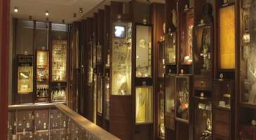 Beyoğlu&rsquo;nun arka sokaklarında gezerken, bir anda kendini edeb&icirc; ve duygusal bir yolculuğun i&ccedil;inde bulman bu kent i&ccedil;in şaşırtıcı sayılmaz. &Ccedil;ukurcuma&rsquo;da nostaljik bir atmosfere sahip olan Masumiyet M&uuml;zesi, klasik bir m&uuml;ze deneyiminden &ccedil;ok daha fazlasını sunuyor. Bu m&uuml;ze, aşkın, takıntıların ve hatıraların somut nesnelerle ifade edildiği eşsiz bir mek&acirc;n olma &ouml;zelliği taşıyor. Hepimizin &ccedil;ekmecesinin bir k&ouml;şesinde, bizim i&ccedil;in b&uuml;y&uuml;k anlamlar taşıyan fakat başkası i&ccedil;in bir anlam ifade etmeyen bir obje vardır. İşte Masumiyet M&uuml;zesi, o &ccedil;ekmecenin dış d&uuml;nyaya taşmış h&acirc;li. Farklı hik&acirc;yelere sahip eşyalarla &ouml;r&uuml;lm&uuml;ş bir romanın &uuml;&ccedil; boyutlu h&acirc;li gibi olan Masumiyet M&uuml;zesi, bir aşk hik&acirc;yesi i&ccedil;inde dolaştığın, hatıralara dokunduğun ve zamanın nasıl ge&ccedil;tiğini anlamayacağın yerlerinden biri. Hadi gel Masumiyet M&uuml;zesi hakkında merak edilenleri birlikte inceleyelim. Masumiyet M&uuml;zesi hakkında Nobel &ouml;d&uuml;ll&uuml; yazar Orhan Pamuk&rsquo;un kaleminden &ccedil;ıkan Masumiyet M&uuml;zesi, 1970&rsquo;ler ve 80&rsquo;ler İstanbul&rsquo;unda ge&ccedil;en bir aşk hik&acirc;yesini anlatıyor. G&uuml;ndelik hayatın y&uuml;zlerce detayını satır aralarında saklayan bu kitapta adı ge&ccedil;en nesnelerin ger&ccedil;ekten var olup olmadığı merak uyandırırken Orhan Pamuk bu merakı sıra dışı bir projeye d&ouml;n&uuml;şt&uuml;rerek romanın m&uuml;zesini kuruyor. M&uuml;zede yer alan bir&ccedil;ok obje, romandaki b&ouml;l&uuml;mlerle birebir ilişkili durumda. Sigara izmaritlerinden elbise par&ccedil;alarına, fotoğraflardan tokalara kadar her detay, kitaptaki hik&acirc;yenin bir sahnesine karşılık geliyor. Bu da edebiyat ile ger&ccedil;ek d&uuml;nya arasında bir k&ouml;pr&uuml; kurarak okuyucuyu bambaşka bir deneyime s&uuml;r&uuml;kl&uuml;yor. Masumiyet M&uuml;zesi&rsquo;ni gezmek, vitrinlere hızlıca bakıp &ccedil;ıkabileceğin bir aktivite olmanın &ouml;tesinde her katı, her odası ve her kutusuyla seni biraz daha hik&acirc;yenin i&ccedil;ine &ccedil;ekiyor. M&uuml;ze, eski İstanbul evlerinin ruhunu taşıyan yapısıyla ziyaret&ccedil;ileri adeta bir zaman t&uuml;neline sokuyor. Ahşap merdivenleri, loş ışıkları ve dar koridorlarıyla dikkat &ccedil;ekici bir atmosfere sahip olan m&uuml;ze, kitaptaki hik&acirc;yenin duygusunu sonuna kadar destekliyor. Klasik m&uuml;ze tanımının &ouml;tesine ge&ccedil;en Masumiyet M&uuml;zesi, her vitrini ve her objesiyle Kemal ile F&uuml;sun&rsquo;un ilişkisine dair bir par&ccedil;ayı g&uuml;n y&uuml;z&uuml;ne &ccedil;ıkarıyor. Roman ile m&uuml;ze arasındaki bağ, Orhan Pamuk&rsquo;un jestiyle daha da kuvvetlenmiş. Yazarın bazı baskıların son sayfalarına yerleştirdiği ve m&uuml;zeye bir kişilik &uuml;cretsiz giriş sağlayan bilet, okuyucunun farklı bir yolculuğa ilk adımını atmasını sağlıyor. Edebiyatın fiziksel bir deneyime d&ouml;n&uuml;şmesine katkı sağlayan bu detay, m&uuml;zeyi d&uuml;nyada benzeri az bulunan bir k&uuml;lt&uuml;r projesi h&acirc;line getiriyor. Anlattığı hik&acirc;ye ve sergilenen objelerle alışılagelen m&uuml;zelerden &ccedil;ok daha farklı bir atmosfer sunan Masumiyet M&uuml;zesi, edebiyat meraklıları başta olmak &uuml;zere fotoğraf tutkunları, romantik ve nostaljik deneyimleri sevenler tarafından mutlaka ziyaret edilmesi gereken yerlerden. Romandan m&uuml;zeye ve diziye Orhan Pamuk&rsquo;un 2008 yılında yayımlanan ve d&uuml;nya &ccedil;apında &ccedil;ok sayıda okura ulaşan romanı Masumiyet M&uuml;zesi, sadece bir aşk hik&acirc;yesinin &ouml;tesinde 1970&rsquo;ler ve 80&rsquo;lerdeki İstanbul&rsquo;u, toplumsal beklentileri, sınıfsal farklılıkları ve bireysel takıntıları b&uuml;y&uuml;k bir ustalıkla işliyor. 2012&rsquo;de m&uuml;ze h&acirc;line getirilen kitap, şimdi de dizi olarak karşımıza &ccedil;ıkıyor. D&ouml;nem dizisi olarak seyirciyle buluşan Masumiyet M&uuml;zesi dizisi, Kemal&rsquo;in i&ccedil;sel d&uuml;nyasını ve F&uuml;sun&rsquo;a olan aşkını daha geniş bir g&ouml;rsel dille ortaya &ccedil;ıkarıyor. Kitaba sadık kalan tarafları ve karakterlerin derinliklerini s&uuml;rd&uuml;rme &ccedil;abasıyla dikkat &ccedil;eken dizi, aşkın iyi ve k&ouml;t&uuml; yanlarını izleyiciyle buluşturuyor. {insightBoxStart}İpucu: Beyoğlu&rsquo;nun hik&acirc;yelerle dolu gecelerine uyanmak istersen, sana en yakın otelleri listeledik. En iyi otel fiyatlarını tek bir yerde g&ouml;rmek, se&ccedil;eceğin otel hakkında bilgi almak ve saniyeler i&ccedil;inde rezervasyon yapmak i&ccedil;in ENUYGUN'da İstanbul otelleri araştırmasına başlayabilirsin.{insightBoxEnd} {hotel_search_form_banner} Masumiyet M&uuml;zesi&rsquo;ne nasıl gidilir? İstanbul&rsquo;un Beyoğlu&rsquo;na bağlı &Ccedil;ukurcuma ile Tophane semtleri arasında yer alan Masumiyet M&uuml;zesi&rsquo;ne ulaşmak, konumu sayesinde olduk&ccedil;a kolay. M&uuml;zeye gitmek i&ccedil;in bir&ccedil;ok alternatif bulunsa da toplu taşıma en pratik yolu diyebiliriz.&nbsp; İstanbul&rsquo;un pek &ccedil;ok noktasından metro, otob&uuml;s veya tramvay hatlarını kullanarak Taksim Meydanı&rsquo;na ulaşabilir, buradan 10-15 dakikalık kısa bir y&uuml;r&uuml;y&uuml;şle m&uuml;zeye varabilirsin. İstikl&acirc;l Caddesi&rsquo;nde T&uuml;nel y&ouml;n&uuml;ne doğru ilerleyerek Galatasaray Lisesi&rsquo;nin hemen yanından &Ccedil;ukurcuma&rsquo;ya doğru inen sokaklara saparak, antikacılar ve sanat galerileriyle dolu keyifli bir rota oluşturabilirsin.&nbsp; Tramvay ile gelmek istersen Tophane durağında inip ortalama 10 dakika y&uuml;r&uuml;yerek m&uuml;zeye ulaşabilirsin. M&uuml;zeye &ouml;zel ara&ccedil;la gitmeyi planlıyorsan &Ccedil;ukurcuma&rsquo;nın dar sokaklarını ve sınırlı park imk&acirc;nlarını g&ouml;z &ouml;n&uuml;nde bulundurmanı tavsiye ederiz.&nbsp; Konum Linki Masumiyet M&uuml;zesi giriş &uuml;creti ve ziyaret saatleri&nbsp; {calismasaatleri}Giriş &uuml;creti Tam bilet 375 TL İndirimli bilet 175 TL Yabancı ziyaret&ccedil;i 750 TL T&uuml;rk&ccedil;e, İngilizce Rus&ccedil;a sesli rehber kişi başı 50 TL (&Ouml;ğretmenler, &ouml;ğrenciler ve 65 yaş &uuml;st&uuml; ziyaret&ccedil;iler i&ccedil;in ge&ccedil;erli.) Orhan Pamuk&rsquo;un Masumiyet M&uuml;zesi adlı kitabının son sayfalarında basılı olan bilet, m&uuml;zenin bilet gişesinde resm&icirc; davetiye olarak ibraz ediliyor. 12 yaşın altındaki &ccedil;ocuklar, ICOM kart sahipleri, lisanslı tur rehberleri, engelli ziyaret&ccedil;iler ve akredite basın mensupları &uuml;cretsiz. A&ccedil;ık olduğu saatler Pazartesi g&uuml;nleri kapalı. Diğer g&uuml;nler 10.00-18.00 saatleri arası a&ccedil;ık. Her yıl 1 Ocak&rsquo;ta, Ramazan ve Kurban bayramlarının ilk g&uuml;nleri kapalı.{/calismasaatleri} {insightBoxStart}Yazar Notu: Biletler salı g&uuml;n&uuml;nden pazar g&uuml;n&uuml;ne kadar 10.00-17.00 saatleri arasında girişin sol tarafındaki gişeden satın alınabilir ya da info@masumiyetmuzesi.org adresine e-posta g&ouml;ndererek grup rezervasyonu yapabilirsin.{insightBoxEnd} Gitmeden &ouml;nce bilmen gerekenler İstanbul&rsquo;da Boğaz manzarası, saraylar ve camiler insanı derinden etkileyen &ouml;nemli noktalar. Masumiyet M&uuml;zesi ise şehrin duygusal hafızasına da dokunan y&ouml;n&uuml;yle &ccedil;ok farklı bir deneyim sunuyor. Bu m&uuml;zede tarihten &ccedil;ok insan hik&acirc;yeleriyle karşılaşır, bir roman kahramanının d&uuml;nyasında dolaşma fırsatı yakalarsın. Masumiyet M&uuml;zesi&rsquo;ni gezmeden &ouml;nce romanı okursan daha &ccedil;ok keyif alabilirsin. Ortalama 1-2 saat s&uuml;recek bir ziyaretle hik&acirc;yenin ruhunu derinden hissedebilir, b&uuml;y&uuml;leyici atmosferinin tadını &ccedil;ıkarabilirsin.&nbsp; &Ccedil;ukurcuma ve &ccedil;evresindeki antikacılar, kafeler ve sanat galerileriyle m&uuml;ze ziyaretini keyifli bir Beyoğlu g&uuml;n&uuml;ne d&ouml;n&uuml;şt&uuml;rebilirsin. Klasik m&uuml;ze gezisinin &ouml;tesinde farklı deneyimler yaşamak istersen gece a&ccedil;ık olan m&uuml;zeler yazımızı inceleyebilirsin.