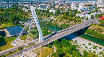 Balkanların en sevilen tatil rotalarından Karadağ&rsquo;ın başkenti Podgoritsa, &ccedil;oğu gezginin aceleyle sahile inmek i&ccedil;in i&ccedil;inden ge&ccedil;ip gittiği bir şehir olsa da aslında ziyaret&ccedil;ilerini b&uuml;y&uuml;leyen bir rota.&nbsp; Morača ve Ribnica nehirlerinin birleştiği noktada yer alan şehir, Osmanlı D&ouml;nemi&rsquo;nden kalma taş sokakları, devasa kanyonların ve g&ouml;llerinin dikkat &ccedil;ektiği eşsiz doğası ile ziyaret&ccedil;ilerini b&uuml;y&uuml;l&uuml;yor. Seyahat planlarının arasında Karadağ varsa klişelerden uzaklaşıp Podgoritsa&rsquo;yı keşfetmeye hazır ol.&nbsp; 1. Zamanın durduğu sokaklar: Podgoritsa'nın tarih&icirc; mirası Podgoritsa'nın ruhunu tam anlamıyla kavrayabilmek i&ccedil;in şehrin tarih&icirc; ve k&uuml;lt&uuml;rel mirasına tanıklık etmek gerekiyor. Sadece birka&ccedil; kilometre alanın i&ccedil;inde hem Osmanlı'nın m&uuml;tevazı mimarisini hem de Ortodoks d&uuml;nyasının ihtişamlı fresklerini bir arada g&ouml;rebilirsin. Y&uuml;zyıllar boyunca farklı medeniyetlere ev sahipliği yapmış bu topraklarda zaman yolculuğuna &ccedil;ıkmaya hazır mısın? {insightBoxStart}Seyahat &Ouml;nerisi: Podgoritsa'nın en g&uuml;zel yanı, o can sıkıcı vize prosed&uuml;rleri ile uğraştırmaması. Karadağ, T&uuml;rkiye Cumhuriyeti vatandaşlarından 30 g&uuml;nl&uuml;k turistik seyahatlerinde vize istemiyor. U&ccedil;ak biletini alıp, sadece pasaportunu &ccedil;antana atman yeterli.&nbsp; &ldquo;Vize stresi olmadan başka nereleri gezebilirim?&rdquo; diyorsan&nbsp;pasaportunla hemen gidebileceğin rotalar yazımıza mutlaka g&ouml;z atmalısın.{insightBoxEnd} Stara Varo&scaron; (Eski Şehir) ve Sahat Kula (Saat Kulesi) Osmanlı'dan g&uuml;n&uuml;m&uuml;ze miras kalan, dar, kıvrımlı ve Arnavut kaldırımlı sokaklarında y&uuml;r&uuml;rken zamanda yolculuk yapıyormuş hissine kapılacaksın. İkinci D&uuml;nya Savaşı'nın yıkıcı bombardımanlarından sağ &ccedil;ıkmayı başaran 16 metre y&uuml;ksekliğindeki Sahat Kula, şehrin t&uuml;m darbelere karşı ayakta kalışının simgesi.&nbsp; Sokaklarda kaybolurken, tarih&icirc; evlerin avlularından taşan sardunyaların ve asmaların fotoğrafını &ccedil;ekebilirsin.&nbsp; İsa&rsquo;nın Dirilişi Katedrali (Hram Hristovog Vaskrsenja) Dış cephesindeki modern ve devasa taş bloklar sade bir yapı izlenimi verse de kapıdan i&ccedil;eri adım attığında Balkanların en g&ouml;rkemli i&ccedil; mekanlarından biriyle karşılaşacaksın. Altın varaklı devasa freskler, detaylı mozaikler ve tavandan s&uuml;z&uuml;len mistik ışık oyunlarının eşsiz ortam ziyaret&ccedil;ilerini b&uuml;y&uuml;l&uuml;yor.&nbsp; &Ccedil;ağdaş mimarinin geleneksel Bizans sanatıyla harmanlandığı yapıda m&uuml;kemmel fotoğraflar &ccedil;ekebilirsin.&nbsp; Dajbabe Manastırı 19. y&uuml;zyılda yerin altına, bir mağaranın i&ccedil;ine ha&ccedil; şeklinde oyularak inşa edilmiş sıra dışı bir manastır. Yapı şehirden biraz uzak olsa da gittiğine değecek g&uuml;zellikte olduğuna emin olabilirsin. Peki, bu devasa manastırın yerin metrelerce altındaki karanlık bir mağaraya sadece insan eliyle nasıl oyulduğunu kendi g&ouml;zlerinle g&ouml;rmek ister misin? Loş ve serin koridorlarında y&uuml;r&uuml;rken, alışkın olduğun dini yapılardan &ccedil;ok daha farklı ve mistik bir deneyim yaşayacaksın. Doğrudan kayaların &uuml;zerine resmedilmiş tarih&icirc; fig&uuml;rleri inceleyebilirsin.&nbsp; {insightBoxStart}Seyahat &Ouml;nerisi: Manastıra giden yollar virajlı olduğundan, ara&ccedil; kiralayacaksan altı y&uuml;ksek bir model se&ccedil;meni tavsiye ederiz.{insightBoxEnd} 2. Nehir kenarında modern ritim: Karadağ'ın dinamik y&uuml;z&uuml; Tarih&icirc; dokunun yanı sıra şehirde hareketli bir hayat da seni bekliyor. Karadağ'ın modern nabzını tutmak istediğinde, şehir seni enerjik ve dinamik y&uuml;z&uuml;yle karşılıyor. Nehir kenarına dizilmiş modern yapıların arasında ve akşam&uuml;st&uuml; dolup taşan caddelerde canlı bir yaşamın ritmini yakalayabilirsin.&nbsp; {insightBoxStart}İpucu: Tarih ve doğanın i&ccedil; i&ccedil;e olduğu bu gizli başkenti keşfetmek sandığından daha kolay! ENUYGUN ile saniyeler i&ccedil;inde Podgoritsa u&ccedil;ak bileti fırsatlarına g&ouml;z atabilir, Balkanların kalbindeki bu eşsiz deneyime hemen ilk adımını atabilirsin.{insightBoxEnd} Milenyum K&ouml;pr&uuml;s&uuml;&nbsp; Morača Nehri'nin &uuml;zerinde 140 metre uzunluğundaki k&ouml;pr&uuml;, 2005 yılından beri şehrin modern sil&uuml;etinin en pop&uuml;ler sembol&uuml;. K&ouml;pr&uuml;den ge&ccedil;erken hem etrafını saran yeşil dağların manzarasını izleyebilir hem de şehrin iki yakasını birleştiren bu harika mimariyi fotoğraflayabilirsin. &Ouml;zellikle akşam saatlerinde, k&ouml;pr&uuml;n&uuml;n etkileyici ışıklandırması eşliğinde nehir kenarında huzur dolu bir y&uuml;r&uuml;y&uuml;ş yapabilirsin.&nbsp; Hercegovačka Caddesi&nbsp; Podgoritsa'nın kalbinin attığı, trafiğe kapalı ve her daim cıvıl cıvıl olan bu caddede, yerel halkın g&uuml;nl&uuml;k ritmine ayak uyduracaksın. Şık bir kafede oturup mis gibi kokusuyla seni kendine &ccedil;eken Karadağ usul&uuml; kahveni yudumlayabilir veya cadde boyunca sıralanan yerel butiklerden alışveriş yapabilirsin. Akşam saatlerinde sokak m&uuml;zisyenlerinin melodileri eşliğinde y&uuml;r&uuml;y&uuml;ş yapabilirsin. Şehrin hareketli hayatına kendini bırakıp, akşamları eğlenceden sonra rahat&ccedil;a oteline d&ouml;nmek istersen Podgoritsa otelleri arasından se&ccedil;im yaparken Hercegovačka Caddesi&rsquo;ne yakın otelleri se&ccedil;ebilirsin.&nbsp; 3. Podgoritsa'nın saklı doğal g&uuml;zellikleri Podgoritsa&rsquo;nın başkent olması doğal g&uuml;zelliklere sahip olmadığı anlamına gelmiyor. Karadağca &ldquo;k&uuml;&ccedil;&uuml;k tepenin dibindeki alan&rdquo; anlamına gelen isminin hakkını veren şehir, etrafını saran tepeler, şelaleler ve milli parklar, beton binaların sadece birka&ccedil; adım &ouml;tesinde doğa ile i&ccedil; i&ccedil;e bir ortam sunuyor.&nbsp; Cijevna Nehri ve Niagara Şelalesi&nbsp; Niagara Şelalesi, Amerika'daki adaşından daha m&uuml;tevazı olsa da &ouml;zellikle bahar aylarında karların erimesiyle iyice coşarak adeta g&ouml;rsel bir ş&ouml;len sunuyor.&nbsp; Keşif dolu bir g&uuml;ne devam ederken rotanı Cijevna Nehri'ne &ccedil;evirebilirsin. Kanyonların arasından d&ouml;k&uuml;len şelaleye karşı oturup y&ouml;resel şarapları deneyebilir ve eşsiz Karadağ mutfağının tadını &ccedil;ıkarabilirsin. Bahar aylarında eriyen karların buz gibi serinliğini y&uuml;z&uuml;nde hissedip, şelalenin etrafında gezinirken g&uuml;r&uuml;l g&uuml;r&uuml;l su sesi t&uuml;m yorgunluğunu alıp g&ouml;t&uuml;recek. Yaz aylarında su seviyesi azalsa da kayalıkların ve turkuaz suların g&ouml;r&uuml;nt&uuml;s&uuml; seni etkilemeye yetecek. Gorica Tepesi&nbsp; Şehre ismini veren bu yeşil alan, Podgoritsa'nın oksijen deposu, yerlilerin ve turistlerin g&uuml;nl&uuml;k ka&ccedil;ış rotası. &Ccedil;am ağa&ccedil;larının yaydığı mis gibi kokular eşliğinde geniş patikalarda y&uuml;r&uuml;y&uuml;ş yapabilir, bisiklete binebilir veya sadece doğanın sesini dinleyebilirsin. Tepenin zirvesine &ccedil;ıkarak şehrin kuşbakışı manzarasını izleyebilirsin. İşkodra G&ouml;l&uuml; Milli Parkı&nbsp; Şehirden arabayla sadece yarım saat mesafede yer alan milli park, Balkanların en b&uuml;y&uuml;k tatlı su g&ouml;l&uuml;ne ev sahipliği yapıyor. Nefes kesici manzara karşısında huzurlu vakitler ge&ccedil;irebilirsin.&nbsp; Su zambaklarının arasında s&uuml;z&uuml;len geleneksel sandallara binebilirsin.&nbsp; Milli parkta, nadir g&ouml;r&uuml;len Tepeli Pelikanları ve diğer kuş t&uuml;rlerini g&ouml;zlemleyebilirsin. {calismasaatleri}Bir Podgoritsalının g&ouml;z&uuml;nden: İşkodra G&ouml;l&uuml;'nde ne yapılır, ne yenir? Tur tekneleri yerine, "Čun"a bin: G&ouml;l&uuml;n kalbine g&uuml;r&uuml;lt&uuml;l&uuml; motorlarla değil, yerel halkın "Čun" adını verdiği geleneksel ahşap kayıklarla gidebilirsin. Nil&uuml;fer tarlalarının ve dar sazlıkların arasından bu geleneksel kayıklarla rahat&ccedil;a ge&ccedil;ebilirsin. Sabah erkenden bir Čun'a atla ve meşhur Tepeli Pelikanları kendi doğal ortamlarında, onları &uuml;rk&uuml;tmeden izle. Men&uuml;ye bakmana gerek yok, hemen "Dimljeni Krap" s&ouml;yle: G&ouml;l kıyısındaki geleneksel restoranlarda sıradan balık yenmez. Şehrin imza lezzetlerinden, g&ouml;le &ouml;zg&uuml; dev bir sazan t&uuml;r&uuml; olan Krap yemeni kesinlikle tavsiye ederiz. S&ouml;ğ&uuml;t ve nar odununda g&uuml;nlerce t&uuml;ts&uuml;lenerek hazırlanan Dimljeni Krap daha masaya gelmeden kokusuyla ağzını sulandıracak. Yanında mısır ekmeğiyle gelen t&uuml;ts&uuml;lenmiş k&uuml;&ccedil;&uuml;k g&ouml;l balığı Ukljeva da harika bir başka se&ccedil;enek. G&uuml;n batımını "Vranac" şarabıyla izle: O muhteşem t&uuml;ts&uuml;lenmiş balığın yanına su veya asitli i&ccedil;ecek s&ouml;ylemek yakışmaz. G&ouml;l&uuml;n hemen kıyısındaki bağlardan elde edilen, Balkanların o meşhur sert ve g&ouml;vdeli kırmızı şarabı Vranac'tan bir kadeh s&ouml;yleyebilirsin. Masanda ev yapımı ke&ccedil;i peyniri, kadehinde Vranac varken Karadağ'ın muhteşem atmosferini iliklerine kadar hissedeceksin.{/calismasaatleri} SunExpress ile b&uuml;t&ccedil;e dostu u&ccedil;uş deneyimi T&uuml;rk Hava Yolları ve Lufthansa&rsquo;nın ortak kuruluşu olan SunExpress, yılların getirdiği tecr&uuml;be ve g&uuml;venle yolcularına kusursuz bir u&ccedil;uş deneyimi sunuyor. Skytrax D&uuml;nya Hava Yolu &Ouml;d&uuml;lleri'nde defalarca "Avrupa'nın En İyi Tatil Hava Yolu" se&ccedil;ilen hava yolu, y&uuml;ksek hizmet kalitesini b&uuml;t&ccedil;e dostu fiyatlarla sunarak Balkanların incisi Podgoritsa tatilini hen&uuml;z g&ouml;ky&uuml;z&uuml;ndeyken başlatıyor. Avrupa'nın en iyi tatil hava yolu: Skytrax tarafından tescilli hizmet kalitesi ve T&uuml;rk misafirperverliğini Alman disipliniyle harmanlayan u&ccedil;uş ekibi sayesinde, rahat bir yolculuk ge&ccedil;irebilirsin. Konforlu u&ccedil;uşlar: Geniş rota ağı ve d&uuml;zenli u&ccedil;uş planlaması sayesinde SunExpress, T&uuml;rkiye&rsquo;nin ana merkezlerinden Podgoritsa&rsquo;ya sunduğu direkt ve aktarmalı u&ccedil;uşlarla Karadağ tatiline en kısa ve en hızlı şekilde başlamanı sağlıyor. Lezzetli u&ccedil;ak i&ccedil;i men&uuml;s&uuml;: U&ccedil;uş esnasında SunCafe&rsquo;nin zengin men&uuml;s&uuml;nden dilediğin atıştırmalıkları, sıcak veya soğuk i&ccedil;ecekleri satın alabilir, yolculuğunu damak zevkine g&ouml;re lezzetlendirebilirsin. Podgoritsa&rsquo;nın yanı sıra Karadağ&rsquo;da g&uuml;zelliği ve k&uuml;lt&uuml;rel varlıkları ile b&uuml;y&uuml;leyen &ccedil;ok sayıda şehir var. En g&uuml;zel Karadağ şehirleri yazımızı okuyarak rotanı genişletebilirsin.&nbsp;