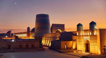 &Ouml;zbekistan'ın a&ccedil;ık hava m&uuml;zesini andıran şehri Hive (Khiva), Kızılkum ve Karakum &ccedil;&ouml;lleri arasında, Amu Derya deltası &uuml;zerinde yer alıyor. Hive (Khiva), Orta Asya'nın en iyi korunmuş ve en mistik şehirlerinden biri. Tarih&icirc; İpek Yolu &uuml;zerinde &ouml;nemli bir durak olan şehir, &ouml;zellikle devasa surlarla &ccedil;evrili i&ccedil; şehri Itchan Kala ile &uuml;nl&uuml;. UNESCO D&uuml;nya Mirası Alanı olan Itchan Kala&rsquo;nın her k&ouml;şesi, hanlıklar d&ouml;neminin ihtişamını ve mimari dehasını yansıtan camiler, medreseler, t&uuml;rbeler ve minarelerle dolu.&nbsp; Hive, tarih ve k&uuml;lt&uuml;r tutkunlarını y&uuml;zyıllar &ouml;ncesine g&ouml;t&uuml;ren, kerpi&ccedil; ve sırlı tuğlanın hakim olduğu tarih&icirc; atmosferiyle &ouml;ne &ccedil;ıkıyor.&nbsp; Hive nasıl bir şehir? Hive UNESCO listesinde yer alan k&uuml;lt&uuml;rel bir kent. Mimarisi, sosyal dokusu veya doğal manzaralarıyla karakteristik bir &ouml;zelliği var. Eğer otantik deneyim, vizesiz &uuml;lke, yerel ve &ouml;zg&uuml;n seyahat deneyimi arıyorsan Hive&rsquo;ye gitmeni &ouml;neririz.&nbsp; Buhara ile Hive arası ne kadar s&uuml;r&uuml;yor? Buhara ile Hive arası yaklaşık 6 saat s&uuml;r&uuml;yor. Genellikle Afrosiyob veya Sharq trenleri ile iki kent arası seyahat ediliyor. Hive&rsquo;de hangi b&ouml;lgede kalmak daha mantıklı? Hive&rsquo;de farklı b&uuml;t&ccedil;elere hitap eden konaklama se&ccedil;enekleri bulunuyor. Merkez oteller y&uuml;r&uuml;me mesafesinde gezilecek yerlere yakın olduğu i&ccedil;in daha &ccedil;ok tercih ediliyor.&nbsp; {calismasaatleri}Hive&rsquo;ye gitmeden &ouml;nce bilmen gerekenler Vize: T&uuml;rkiye Cumhuriyeti vatandaşları &Ouml;zbekistan&rsquo;a vizesiz giriş yapabiliyor. Ge&ccedil;erli bir pasaportun varsa kolayca seyahat edebilirsin. En iyi ay: Hive&rsquo;yi gezmek i&ccedil;in en ideal aylar nisan ve haziran ile eyl&uuml;l ve ekim arası. Para birimi: &Ouml;zbekistan&rsquo;ın para birimi &Ouml;zbekistan somu.&nbsp; (&Ccedil;oğu yerde nakit ge&ccedil;erli. Kredi kartı kullanma oranı d&uuml;ş&uuml;k)&nbsp; Dil: Resmi dil &Ouml;zbek&ccedil;e. Turistik b&ouml;lgelerde İngilizce oranı ise d&uuml;ş&uuml;k. Kamu kurumlarında ise Rus&ccedil;a konuşma oranı y&uuml;ksek.&nbsp; Ulaşım: Hive&rsquo;ye en yakın havalimanı Urgen&ccedil; (Urgench Airport &ndash; UGC). Hive&rsquo;ye ara&ccedil;la yaklaşık 35 dakika s&uuml;r&uuml;yor. Hive&rsquo;yi keşfederken genellikle y&uuml;r&uuml;yerek bir&ccedil;ok yeri g&ouml;rebilirsin.&nbsp; Elektrik: Priz tipi C ve F olduğu i&ccedil;in T&uuml;rkiye ile aynı priz kullanımı var. İnternet: Turist SIM kartını Urgen&ccedil; Havalimanı&rsquo;nda kolayca alabilirsin.{/calismasaatleri} {insightBoxStart}Hive seyahatin i&ccedil;in ipu&ccedil;ları Kombine bilet: Itchan Kala tarihi bir b&ouml;lge ve i&ccedil;inde birden fazla &uuml;cretli yapı bulunuyor. Bu y&uuml;zden kombine bilet alarak gezmen daha ekonomik bir se&ccedil;enek olur. Unutmadan! Itchan Kala kombine bileti 2 g&uuml;n ge&ccedil;erli.&nbsp; En iyi fotoğraf noktası: İslam Hoca Minaresi şehrin en y&uuml;ksek tepesi olduğu i&ccedil;in g&uuml;zel bir manzara sunuyor. Itchan Kala&rsquo;yı da tepeden g&ouml;rebiliyorsun. Kunya Ark&rsquo;ın seyir terasından da panoramik bir manzara seyredebilirsin. Yeme-i&ccedil;me: Hive&rsquo;de plov, shivit oshi (yeşil erişte) ve lagman gibi &ouml;zbek mutfağı tatlarını deneyebilirsin.{insightBoxEnd} 1. Itchan Kala (Eski Şehir) Hive&rsquo;de gezilecek en iyi yerler, surlarla &ccedil;evrili UNESCO D&uuml;nya Mirası Listesi alanı Itchan Kala (İ&ccedil;han Kale) i&ccedil;erisinde yoğunlaşıyor. Itchan Kala, şehrin tarih&icirc; kent merkezi. Burası, surlarla &ccedil;evrili devasa bir a&ccedil;ık hava m&uuml;zesi. Kerpi&ccedil;ten yapılmış g&uuml;&ccedil;l&uuml; duvarlar, eski şehri koruma altına alıyor. Orta Asya mimarisinin en saf &ouml;rneklerini g&ouml;rebileceğin Itchan Kala'da y&uuml;r&uuml;mek ise binlerce yıllık ge&ccedil;mişini hissetmek demek. Itchan Kala surlarının i&ccedil;inde 50'den fazla tarih&icirc; yapıyı gezebilirsin. Bunlar yapılar arasında etkileyici saraylar, camiler, medreseler ve t&uuml;rbeler var. Kuhna Ark kalesi, Kalta Minor'un turkuaz &ccedil;inileri ve Cuma Camii'nin ahşap s&uuml;tunları ise &ouml;zellikle g&ouml;r&uuml;lmeye değer. Itchan Kala&rsquo;nın dar sokaklarda dolaşarak, İpek Yolu efsanelerini keşfe &ccedil;ıkabilirsin. Konum Linki 2. Kalta Minor Hive&rsquo;nin en ikonik sembollerinden olan Kalta Minor, yapımı yarım kalmış efsanevi bir minare. Kalta Minor, g&ouml;z alıcı turkuaz ve mavi &ccedil;inileriyle hemen fark ediliyor. 1851 yılında Muhammed Emin Han tarafından Hive Hanlığı d&ouml;neminde yapımına başlanan Kalta Minor, minare olarak tasarlanmış, ancak inşası yarım kalmış. Kalta Minor, kısa ve geniş yapısıyla hemen dikkat &ccedil;ekiyor ve ismi "Kısa Minare" anlamına geliyor.&nbsp; Kalta Minor&rsquo;un y&uuml;ksekliği 29 metre, &ccedil;apı ise 14 metre. &Ccedil;ini kaplamaları benzersiz bir g&uuml;zelliğe sahip minare, mavi ve yeşil tonlarla s&uuml;sl&uuml;. Kalta Minor, Hive'nin eski şehir b&ouml;lgesi olan Itchan Kala'da yer alıyor ve UNESCO tarafından D&uuml;nya Mirası olarak korunuyor.&nbsp; Minare, tamamlanmamış olmasına rağmen, zengin seramik s&uuml;slemeleriyle Orta Asya mimarisinin başyapıtlarından biri sayılıyor. Kalta Minor, g&uuml;n&uuml;m&uuml;zde Hive'nin en &ccedil;ok fotoğraflanan ve bilinen sembol&uuml;. Konum Linki 3. Kunya Ark (Eski Saray) Hive'nin en eski ve en &ouml;nemli yapılarından biri Kunya Ark. Burası Itchan Kala'nın batı duvarına bitişik olarak inşa edilmiş bir mimari şaheser. 17. y&uuml;zyılda yapılan Kunya Ark, hanların yaşadığı bir saray kompleksi. Kunya Ark, adeta "şehir i&ccedil;inde şehir" g&ouml;revini &uuml;stlenmiş. Burası y&uuml;ksek kalın duvarları ile şehrin geri kalanından ayrılıyor. Kunya Ark&rsquo;ın mimarisinde de geleneksel &Ouml;zbek tasarımları ve &ccedil;ini s&uuml;slemeleri ile olduk&ccedil;a dikkat &ccedil;ekici. Kunya Ark&rsquo;ın i&ccedil;erisinde saray, taht odası, cami, avlular, darphane ve harem gibi bir&ccedil;ok b&ouml;l&uuml;m&uuml; gezebilirsin. Kale, ayrıca askeri bir &uuml;s olarak cephanelik ve zindanlara da sahip. G&uuml;n&uuml;m&uuml;zde rehberli turlar ile kalenin i&ccedil;indeki yapılara &ouml;zel geziler d&uuml;zenleniyor. &Ouml;zellikle g&ouml;zetleme kulesine &ccedil;ıkarak Itchan Kala'nın muhteşem panoramik manzarasını izlemek &ccedil;ok sevilen bir etkinlik. Konum Linki 4. Cuma Camii Hive'in UNESCO D&uuml;nya Mirası Listesi&rsquo;ndeki simgesel yapılarından Cuma Camii, eşsiz mimarisiyle dikkatleri &ccedil;ekiyor. Cami, geleneksel Orta Asya camilerinden farklı bir yapıya sahip. Dışarıdan olduk&ccedil;a sade g&ouml;r&uuml;nen Cuma Camii&rsquo;nin i&ccedil;ine girince bir s&uuml;tun ormanı ile karşılaşacaksın. Cami, d&uuml;z bir &ccedil;atıya sahip ve bu &ccedil;atı 200'den fazla ahşap s&uuml;tunla destekleniyor. Bu s&uuml;tunların bazıları, 10. y&uuml;zyıla kadar uzanan &ccedil;ok eski par&ccedil;alar. 10. y&uuml;zyılda inşa edilen ve 18. y&uuml;zyılda yenilenen Cuma Camii&rsquo;nde avlu yerine, yapının i&ccedil;inden ışık girmesini sağlayan b&uuml;y&uuml;k boşluklar var. Bu ilgin&ccedil; tasarım, i&ccedil; mek&acirc;na loş ve mistik bir atmosfer katıyor. Caminin s&uuml;tunlarının her biri farklı bir ustalıkla oyulmuş ve &ouml;zenle s&uuml;slenmiş. Cuma Camii, sadece bir ibadethane değil, aynı zamanda Hive'nin tarihini ve ahşap oyma sanatını sergileyen &ouml;nemli bir anıt.&nbsp; Konum Linki 5. Taş Avlu Sarayı (Toshhovli Palace) Hive&rsquo;nin bir diğer &ouml;nemli simgesi olan Taş Avlu Sarayı, 19. y&uuml;zyıldan kalma bir eser. Itchan Kala&rsquo;nın doğu kısmındaki saray, han ve ailesi i&ccedil;in bir yaşam alanı olarak tasarlanmış. G&ouml;rkemli s&uuml;slemeleriyle dikkat &ccedil;eken saray, adını da geniş taş avlusundan alıyor. 150&rsquo;den fazla odası ve &uuml;&ccedil; b&uuml;y&uuml;k avlusu olan Taş Avlu Sarayı&rsquo;ın duvarları ise &Ouml;zbek motifleriyle s&uuml;slenmiş renkli &ccedil;inilerle kaplı. Saray, bu &ouml;zellikleriyle Orta Asya mimarisinin en g&uuml;zel &ouml;rneklerinden biri olarak g&ouml;steriliyor.&nbsp; Toshhovli, "taş ev" anlamına geliyor ve 4 avludan oluşuyor. Taş Avlu Sarayı, sadece bir konut değil, aynı zamanda y&ouml;netim merkezi olarak da kullanılmış. Sarayın harem kısmı, hanın eşleri ve ailesi i&ccedil;in ayrılmış. Ayrıca sarayda resmi t&ouml;renler ve toplantılar i&ccedil;in &ouml;zel alanlar bulunuyor. Taş Avlu Sarayı&rsquo;nın detaylı oymaları ile &ccedil;ini s&uuml;slemeleri, sarayın sanat ve estetik y&ouml;n&uuml;n&uuml; &ouml;ne &ccedil;ıkarıyor. Konum Linki 6. Pehlevan Mahmud T&uuml;rbesi Pehlevan Mahmud T&uuml;rbesi, Hive&rsquo;nin en &ouml;nemli manev&icirc; ve tarih&icirc; yapılarından biri olarak g&ouml;r&uuml;lmeye değer. T&uuml;rbe, 14. y&uuml;zyılda yaşamış şair, filozof ve g&uuml;reş&ccedil;i Pehlevan Mahmud&rsquo;a adanmış. Pehlevan Mahmud, hem fiziksel hem de manev&icirc; g&uuml;c&uuml; ile Hive halkı tarafından kahraman olarak kabul ediliyor. Şiirleriyle de tanınan bu &ouml;nemli fig&uuml;r, halk arasında bilge bir kişi olarak saygı g&ouml;r&uuml;yor. Pehlevan Mahmud T&uuml;rbesi ise g&ouml;z alıcı mavi ve yeşil &ccedil;inileri ile &uuml;nl&uuml;. Yapının kubbesi de olduk&ccedil;a g&ouml;rkemli, ayrıca i&ccedil; kısmındaki s&uuml;slemeler ve yazıtlar &ccedil;ok etkileyici. Pehlevan Mahmud T&uuml;rbesi, zarif &ccedil;ini s&uuml;slemeleri ve kubbesiyle de &ouml;ne &ccedil;ıkıyor. Etkileyici yapı, Itchan Kala b&ouml;lgesinde ve Hive hanlarının mezarlarının bulunduğu bir kompleksin merkezinde yer alıyor. T&uuml;rbe, sadece bir anıt değil, aynı zamanda da bir ibadet yeri. Ziyaret&ccedil;iler, burada dua ederek Pehlevan Mahmud&rsquo;un mirasını anıyor.&nbsp; Konum Linki 7. İslam Hoca Minaresi ve Medresesi Hive&rsquo;nin en dikkat &ccedil;ekici tarih&icirc; yapılarından biri de İslam Hoca Minaresi ve Medresesi. Bu kompleks, 20. y&uuml;zyılın başında, 1908 yılında inşa edilmiş. İslam Hoca, Hive&rsquo;nin son baş veziri ve bu eserler, onun anısına yapılmış. Minare, 57 metre y&uuml;ksekliğiyle Hive&rsquo;nin en y&uuml;ksek yapısı ve şehrin her yerinden g&ouml;r&uuml;lebiliyor. İnce uzun tasarımıyla dikkat &ccedil;eken minare, geleneksel Orta Asya minare mimarisinin zarif bir &ouml;rneği. Minarenin renkli &ccedil;ini s&uuml;slemeleri de g&ouml;r&uuml;lmeye değer g&uuml;zellikte. Medrese ise minarenin hemen yanında yer alıyor ve bir zamanlar dini eğitim verilen &ouml;nemli bir merkez. G&uuml;n&uuml;m&uuml;zde ise medrese, k&uuml;lt&uuml;rel ve mimari a&ccedil;ıdan &ouml;nemli turistik bir mek&acirc;n olarak ziyaret ediliyor. Minarenin izleme alanlarına &ccedil;ıkarak, Hive&rsquo;nin etkileyici manzarasını izleyebilir, kartpostal g&uuml;zelliğinde fotoğraflar &ccedil;ekebilirsin. Kompleks, Itchan Kala b&ouml;lgesinde yer alıyor ve Hive&rsquo;nin ge&ccedil;mişini ve İslam k&uuml;lt&uuml;r&uuml;n&uuml; &ccedil;arpıcı bir şekilde yansıtıyor.&nbsp; Konum Linki {insightBoxStart}İpucu: ENUYGUN&rsquo;dan kolayca u&ccedil;ak bileti alabilir, dilediğin yeri uygun fiyatlarla keşfedebilirsin. Şimdi seyahatinin ilk adımı olan &Ouml;zbekistan u&ccedil;ak bileti almak i&ccedil;in tıkla.{insightBoxEnd} 8. Nurullaboy Sarayı Nurullaboy Sarayı, sadece Hive&rsquo;nin değil, &Ouml;zbekistan&rsquo;ın de en dikkat &ccedil;ekici yapılarından biri. Saray, 20. y&uuml;zyılın başlarında Hive Hanı Asfandiyar Han tarafından yaptırılmış. Avrupa mimarisi ile geleneksel Orta Asya tarzının birleşimiyle inşa edilen Nurullaboy Sarayı, bu &ouml;zelliğiyle Hive&rsquo;nin klasik kerpi&ccedil; mimarisinden farklı bir estetik sunuyor. Sarayın geniş avlulara, s&uuml;sl&uuml; tavanları ve zarif ahşap iş&ccedil;iliği, &ouml;zellikle dikkat &ccedil;ekiyor. Nurullaboy Sarayı, Hive Hanlığı d&ouml;neminin son zaferlerini ve k&uuml;lt&uuml;rel zenginliğini yansıtıyor. G&uuml;n&uuml;m&uuml;zde m&uuml;ze olarak kullanılan sarayın odalarında gezerek d&ouml;nemin yaşam tarzını yansıtan eşyaları g&ouml;rebilirsin. Nurullaboy Sarayı, Hive&rsquo;nin UNESCO D&uuml;nya Mirası stat&uuml;s&uuml;ne de katkı sağlayan &ouml;nemli bir eser. Konum Linki {insightBoxStart}Yazar Notu: Saray, Itchan Kala'nın hemen dışındaki Dishan Kala b&ouml;lgesinde bulunuyor. Itchan Kala'deki ana turistik yoğunluğun dışında kalan saraya ulaşım i&ccedil;in Itchan Kala'dan y&uuml;r&uuml;y&uuml;ş yapmak veya taksi kullanmak gerekiyor.{insightBoxEnd} 9. Ota Darvoza (Batı Kapısı) Itchan Kala eski şehrin ana girişi olan Ota Darvoza, 19. y&uuml;zyılda inşa edilmiş ve şehrin simgesi h&acirc;line gelmiş etkileyici bir eser. &ldquo;Batı Kapısı&rdquo; anlamına gelen Ota Darvoza, tuğladan yapılmış y&uuml;ksek kuleleri ve mavi &ccedil;inileriyle dikkat &ccedil;ekiyor. Kapının &uuml;zerindeki yazılar ve s&uuml;slemeler ise d&ouml;nemin ustalarının ince iş&ccedil;iliğini g&ouml;steriyor. Ota Darvoza, sadece bir giriş kapısı değil, aynı zamanda Hive&rsquo;nin tarihini anlatan bir anıt. Kapının arkasında tarih&icirc; medreseler ve camiler, &ccedil;arpıcı manzarayı tamamlıyor. Ge&ccedil;mişte hanlar ile t&uuml;ccarlar bu kapıdan ge&ccedil;erek Hive&rsquo;ye giriyorlardı ve bu atmosfer hala canlı. G&uuml;n&uuml;m&uuml;zde Ota Darvoza, turistlerin Hive&rsquo;yi keşfetmeye başladığı ilk noktalardan biri. Akşam saatlerinde kapı ve &ccedil;evresi aydınlatılıyor, bu da gece fotoğraf&ccedil;ılığı i&ccedil;in b&uuml;y&uuml;leyici bir atmosfer yaratıyor. Konum Linki 10. Polvon Darvoza Kapısı Tarih&icirc; Itchan Kala'nın doğu giriş kapısı olan Polvon Darvoza, 19. y&uuml;zyıldan kalan bir hazine. Kapı, Hive&rsquo;nin &ouml;nemli ticaret yollarına a&ccedil;ılıyor. Polvon Darvoza, &ldquo;Pehlivan Kapısı&rdquo; anlamına geliyor ve kapı, y&uuml;ksek kulelerindeki tuğla işlemeleriyle dikkat &ccedil;ekiyor. Kapının giriş kısmında ise d&ouml;nemin mimari s&uuml;slemelerini yansıtan g&uuml;zel yazıtları g&ouml;r&uuml;lebilir. Polvon Darvoza, Hive&rsquo;nin canlı ticaret yaşamının bir sembol&uuml; olarak &ouml;zenle korunuyor. Ge&ccedil;mişte t&uuml;ccarlar ve gezginler, bu kapıdan şehre giriş yapıyorlarmış. Kapının &ccedil;evresinde g&uuml;n&uuml;m&uuml;zde de hareketli pazar yerleri ve zanaatk&acirc;r d&uuml;kk&acirc;nları var. Polvon Darvoza, ziyaret&ccedil;ilerin şehrin tarihini hissetmeye başladığı &ouml;nemli bir nokta ve Hive&rsquo;nin k&uuml;lt&uuml;rel mirasının g&ouml;rkemli bir par&ccedil;ası. Konum Linki {{campaignsSlider}} 11. Bakcha Darvoza Kapısı Bakcha Darvoza, tarih&icirc; Itchan Kala'nin kuzey tarafında yer alıyor ve eski şehir surlarının d&ouml;rt ana girişinden biri. 19. y&uuml;zyılda inşa edilen g&ouml;rkemli kapı, Hive&rsquo;nin &ouml;nemli savunma yapıları arasında. Bakcha Darvoza, tuğladan yapılan g&uuml;&ccedil;l&uuml; duvarları ve y&uuml;ksek kuleleriyle dikkat &ccedil;ekiyor. Mimari tasarım ise Hive&rsquo;nin geleneksel tarzını yansıtıyor. Ge&ccedil;mişte bu kapı, şehrin kuzey b&ouml;lgeleriyle ve dış mahalleleri birbirine bağlıyordu. Kerpi&ccedil; ve tuğla kullanılarak inşa edilmiş Bakcha Darvoza, kalın sur duvarlarının &ouml;nemli bir par&ccedil;ası. Diğer ana kapılar gibi Bakcha Darvoza da şehri korumak amacıyla g&uuml;&ccedil;l&uuml; kulelerle desteklenmiş. G&uuml;n&uuml;m&uuml;zde ise Bakcha Darvoza, &ccedil;evresindeki geleneksel evler ve eski sokaklarıyla sevilen bir turistik alan.&nbsp; Konum Linki 12. Kosh-Darvoza Kapısı Itchan Kala'nın g&uuml;ney girişi olan Kosh-Darvoza, şehrin ana surlarının d&ouml;rt temel girişinden biri. &ldquo;Kosh&rdquo; kelimesi, &ccedil;ift anlamına geliyor, bunun nedeni ise kapının iki ge&ccedil;itli bir yapı olarak tasarlanması. 19. y&uuml;zyılda inşa edilen kapı, savunma ve ticaret amacıyla inşa edilmiş. Tuğla duvarları, kemerli ge&ccedil;itleri ve kuleleriyle dikkat &ccedil;eken Kosh-Darvoza, Hive&rsquo;nin mimari estetiğini yansıtıyor. Kosh-Darvoza, Itchan Kala'nın g&uuml;neybatı kısımlarına ve şehir dışındaki yerleşim yerlerine a&ccedil;ılıyor. Kapının bu konumu, ge&ccedil;mişte Hive'nin ticari ve sosyal yaşamı a&ccedil;ısından &ouml;nemli bir rol oynamış. G&uuml;n&uuml;m&uuml;zde ise Kosh-Darvoza, &ccedil;evresindeki eski pazar yerleri ve geleneksel yapılar ile Hive&rsquo;nin tarih&icirc; kimliğini koruyor. Konum Linki 13. Muhammed Emin Han Medresesi Hive şehrinin en b&uuml;y&uuml;k ve en g&ouml;rkemli medreselerinden biri Muhammed Emin Han Medresesi. Bu etkileyici tarih&icirc; yapı, 1851 yılında Muhammed Emin Han tarafından inşa edilmiş. Medrese, 120&rsquo;den fazla odalarıyla d&ouml;nemin en &ouml;nemli eğitim merkezlerinden biri olarak hizmet vermiş. Yapının cephesi, mavi ve yeşil geleneksel &Ouml;zbek &ccedil;ini s&uuml;slemeleriyle s&uuml;sl&uuml; olduğu i&ccedil;in g&ouml;z alıcı bir estetiğe sahip. Avlu ise geniş ve simetrik planıyla dikkat &ccedil;ekiyor.&nbsp; Muhammed Emin Han Medresesi, Itchan Kala (İ&ccedil; Kale) batı giriş kapısının hemen yanında yer alıyor. Medrese, yanında y&uuml;kselen Kalta Minor Minaresi ile birlikte Hive&rsquo;nin otantik dokusunu da tamamlıyor. G&uuml;n&uuml;m&uuml;zde turizme a&ccedil;ılan Muhammed Emin Han Medresesi, hem eğitim hem de sanat a&ccedil;ısından Hive&rsquo;nin en &ccedil;ok ziyaret edilen turistik mek&acirc;nlarından biri. Konum Linki 14. Allakuli Han Medresesi ve Kervansarayı 19. y&uuml;zyılda yaptırılan Allakuli Han Medresesi ve Kervansarayı, Hive şehrinin &ouml;nemli tarih&icirc; hazinelerinden. 1835 yılında inşa edilen medrese, Itchan Kala&rsquo;nın doğu kısmında yer alıyor. Simetrik yapısı ve renkli &ccedil;ini s&uuml;slemeleriyle dikkat &ccedil;eken medrese, g&uuml;n&uuml;m&uuml;zde de Hive&rsquo;nin k&uuml;lt&uuml;rel ve dini hayatında &ouml;nemli bir yere sahip. Kervansaray ise medresenin hemen yanında yer alıyor ve geniş bir avlu ile depolama alanlarına sahip. Burası, İpek Yolu t&uuml;ccarları i&ccedil;in bir konaklama ve ticaret merkezi olarak kullanılmış. G&uuml;n&uuml;m&uuml;zde ise kervansaray, Hive&rsquo;nin turistik pazarlarından biri haline gelmiş durumda. Bu otantik pazarda el yapımı halılar, seramikler ve geleneksel hediyelik eşyalar satın alabilirsin. Allakuli Han Medresesi, ticari ve k&uuml;lt&uuml;rel ge&ccedil;mişi yansıtan bir kompleks olarak turistlerin ilk uğradığı yerlerden. Konum Linki 15. Khorezm İpek M&uuml;zesi Khorezm İpek M&uuml;zesi, geleneksel İpek Yolu k&uuml;lt&uuml;r&uuml;n&uuml; ve ipek &uuml;retim s&uuml;re&ccedil;lerini tanıtmak i&ccedil;in kurulmuş. M&uuml;zenin etkileyici koleksiyonları, Hive&rsquo;nin İpek Yolu &uuml;zerindeki rol&uuml;n&uuml; ve ipek&ccedil;iliğin tarihini yansıtıyor. M&uuml;ze, aynı zamanda ziyaret&ccedil;ilere b&ouml;lgenin zengin dokuma k&uuml;lt&uuml;r&uuml;n&uuml; de tanıtıyor. Sergilerde geleneksel y&ouml;ntemlerle &uuml;retilmiş ipek kumaşları inceleyebilirsin. M&uuml;zede ipek b&ouml;ceği yetiştiriciliği ile ilgili bilgiler de veriliyor. İpek dokuma tezgahları ve eski el sanatları ara&ccedil;larını yakından inceleyebilirsin. At&ouml;lyelere katılarak da ipek kumaş &uuml;retiminin her aşamasını &ouml;ğrenebilirsin. Khorezm Silk Museum, hem k&uuml;lt&uuml;rel hem de tarih&icirc; a&ccedil;ıdan Hive&rsquo;nin zengin el sanatları mirasını keşfetmek i&ccedil;in ideal bir yer. Konum Linki 16. Şergazikhan Medresesi Hive şehrindeki en eski eğitim yapılarından biri de Şergazikhan Medresesi. 1710&ndash;1713 yılları arasında inşa edilen medrese, Hive Hanı Şirgazi Han tarafından yaptırılmış. Itchan Kala&rsquo;nın kalbinde yer alan medrese, klasik Orta Asya medrese mimarisinin g&uuml;zel bir &ouml;rneği. Yapı, geniş avlusu, h&uuml;cre odaları ve s&uuml;slemeli bir giriş kapısı ile dikkat &ccedil;ekiyor. Medresenin duvarlardaki k&ucirc;fi yazılar ve mavi &ccedil;inileri de &ouml;zellikle g&ouml;r&uuml;lmeye değer. Şergazikhan Medresesi&rsquo;nde uzun yıllar boyunca bilim ve din alanında eğitimler verilmiş. Burada d&ouml;nemin &uuml;nl&uuml; bilginleri de &ouml;zel dersler vermiş. G&uuml;n&uuml;m&uuml;zde ise medrese, ziyaret&ccedil;ilere a&ccedil;ık bir tarih&icirc; mek&acirc;n olarak ilgi g&ouml;r&uuml;yor. Yapı, Hive&rsquo;nin k&uuml;lt&uuml;rel dokusunu yaşatıyor, aynı zamanda &Ouml;zbekistan&rsquo;ın ge&ccedil;miş ilim ve sanatının bir mirası olarak korunuyor. Konum Linki 17. Qutlugh Murad İnaq Medresesi Hive&rsquo;nin &ouml;nemli bir tarih&icirc; eseri olan Qutlugh Murad İnaq Medresesi, Itchan Kala'nın &ccedil;ok ziyaret edilen yerlerinden. Medrese, 19. y&uuml;zyılın başlarında inşa edilmiş ve adını d&ouml;nemin &uuml;nl&uuml; y&ouml;neticilerinden Kutlug Murad İnaq&rsquo;tan alıyor. Medrese, şehrin merkezine yakın bir konumda ve diğer yapılarla birlikte gezilebilir.&nbsp; Geleneksel Orta Asya mimarisi stilini yansıtan medrese, iki katlı h&uuml;crelerden oluşan b&uuml;y&uuml;k bir avlu etrafında tasarlanmış. Medresenin dış cephesi ve eyvanları ise d&ouml;nemin karakteristik sırlı tuğlalarıyla s&uuml;sl&uuml;. Qutlugh Murad İnaq Medresesi, b&ouml;lgedeki mimari gelişmenin bir simgesi olarak Hive&rsquo;nin k&uuml;lt&uuml;rel mirasını g&ouml;zler &ouml;n&uuml;ne seriyor. Konum Linki 18. Qozi Kalon Medresesi (M&uuml;zik Sanatı M&uuml;zesi) Qozi Kalon Medresesi, Itchan Kala'nın &ouml;nemli tarih&icirc; yapıları arasında. Qozi Kalon (B&uuml;y&uuml;k Kadı) tarafından inşa ettirilmiş. Medrese, Hive'deki eğitim kurumlarının son &ouml;rneklerinden biri olarak kabul ediliyor. Geleneksel Hive medrese mimarisinin zarif &ouml;rneklerinden biri olan Qozi Kalon Medresesi, kemerli pencereleri ve s&uuml;slemeli giriş kapısıyla da dikkat &ccedil;ekiyor. G&uuml;n&uuml;m&uuml;zde Qozi Kalon Medresesi, &ldquo;M&uuml;zik Sanatı M&uuml;zesi&rdquo; olarak kullanılıyor. M&uuml;ze koleksiyonlarında ise geleneksel Harezm m&uuml;ziğine ait &ccedil;algılar ve sanat eserleri sergileniyor. Burada &Ouml;zbek m&uuml;ziğinin tarihini ve k&uuml;lt&uuml;rel gelişimini keşfedebilirsin. Medresenin odaları, sanatın ve eğitimin birleştiği mistik atmosferleri ile ge&ccedil;mişin sanat ruhunu g&uuml;n&uuml;m&uuml;ze taşıyor. Konum Linki 19. Amir Tura Medresesi Itchan Kala'nın merkezine yakın konumdaki Amir Tura Medresesi, 19. y&uuml;zyılın sonlarında, Harezm Hanlığı d&ouml;neminde inşa edilmiş. Medrese, d&ouml;neminde dini ve hukuki ilimlerin &ouml;ğretildiği bir eğitim merkezi olarak hizmet vermiş. Hive'nin kendine has kerpi&ccedil; mimarisi stilini g&ouml;rebileceğin medrese,&nbsp; k&uuml;&ccedil;&uuml;k olmasına rağmen avlusu ve &ouml;ğrenci odalarıyla klasik bir medrese d&uuml;zenine sahip. Medresenin dış cephesinde ve girişinde de d&ouml;nemin sade ancak etkileyici tuğla iş&ccedil;iliğini g&ouml;rebilirsin. Amir Tura Medresesi, g&uuml;n&uuml;m&uuml;zde Hive&rsquo;nin tarih&icirc; mirasını yaşatan &ouml;nemli ziyaret noktalarından biri. Medrese, şehrin k&uuml;lt&uuml;rel dokusuna sessiz bir zarafet katıyor, ayrıca Hive&rsquo;nin eğitim ge&ccedil;mişine ışık tutuyor. Konum Linki 20. Matniyaz Divanbegi Medresesi Itchan Kala'da yer alan Matniyaz Divanbegi Medresesi, 1905 yılından kalma bir eser. Itchan Kala&rsquo;nın tarih&icirc; dokusunu tamamlayan medrese, geleneksel Hive mimarisinin zarif &ouml;zelliklerini taşıyor. Yapı, tuğladan yapılmış cephesi, kemerli giriş kapısı ve k&uuml;&ccedil;&uuml;k kubbeleriyle dikkat &ccedil;ekiyor. Medrese, Harezm Hanlığı'nın son d&ouml;nemlerinde yapılan b&uuml;y&uuml;k &ccedil;aplı İslami eğitim yapılarından biri olmasıyla da &ouml;ne &ccedil;ıkıyor.&nbsp; Ge&ccedil;mişte ilim ve din eğitimi verilen bir merkez olan Matniyaz Divanbegi Medresesi, &ouml;ğrenci h&uuml;creleri, derslikler ve geniş bir avluya sahip. G&uuml;n&uuml;m&uuml;zde ise medrese, aslına uygun olarak restore edilerek turistlerin ziyaretine a&ccedil;ılmış durumda. Medresenin sessiz atmosferi, ge&ccedil;mişin eğitim ve k&uuml;lt&uuml;r hayatını hissetmek i&ccedil;in ideal. Konum Link 21. Porta sud Dishan Kala (Dış Kale) Dishan Kala (Dış Kale), Itchan Kala'yı &ccedil;evreleyen dış surlarını ifade ediyor. Porta sud Dishan Kala ise bu dış surların etkileyici g&uuml;ney kapısı. Kapı, 19. y&uuml;zyılda inşa edilmiş ve şehrin dış savunma sisteminin &ouml;nemli bir par&ccedil;ası. Tuğla duvarları ve kemerli ge&ccedil;iş yapısı ile dikkat &ccedil;eken kapının mimari tarzı ise Hive&rsquo;nin geleneksel savunma mimarisini yansıtıyor. Porta sud Dishan Kala, ge&ccedil;mişte Hive&rsquo;ye g&uuml;neyden gelen t&uuml;ccarların ve yolcuların giriş noktası olarak kullanılmış. Kapı, aynı zamanda şehirde ticaret ve g&uuml;venlik a&ccedil;ısından stratejik bir &ouml;neme sahip. G&uuml;n&uuml;m&uuml;zde bu tarih&icirc; kapı, ziyaret&ccedil;ilere eski Hive&rsquo;nin sınırlarını ve yapısını g&ouml;steren &ouml;nemli bir durak. Kapının etrafında eski sur kalıntıları ve geleneksel yapıları da keşfe &ccedil;ıkabilirsin. Konum Linki 22. Hive Memorial Park Itchan Kala'nın hemen yakınındaki Memorial Park (Anıt Parkı), şehrin sevilen gezi alanlarından biri. Park, Hive'nin k&uuml;lt&uuml;rel mirasını anmak ve yaşatmak amacıyla kurulmuş. Park, aynı zamanda dinlenme ve nefes alma imkanı sunan bir yeşil alan. Memorial Park, tarih&icirc; yapıların yoğunluğundan uzaklaşmak ve dinlenmek i&ccedil;in de ideal bir yer.&nbsp; Memorial Park, Hive'nin &ouml;nemli fig&uuml;rlerine adanmış anıtlar ve heykelleriyle dikkat &ccedil;ekiyor. Aynı zamanda parkta Hive'nin tarihine ışık tutan bazı k&uuml;lt&uuml;rel objeler de sergileniyor. Memorial Park, tarih&icirc; eserleri g&ouml;rmek isteyen turistler i&ccedil;in de bir toplanma ve başlangı&ccedil; noktası.&nbsp; Konum Linki 23. Hive tarih&icirc; &ccedil;arşıları Hive, birbirinden renkli &ccedil;arşılarla &ccedil;evrili. İpek Yolu &uuml;zerinde olan şehirde bu &ccedil;arşılar, her d&ouml;nemde ticaretin kalbini oluşturmuş. &Ccedil;arşılar, geleneksel olarak medreselerin ve kervansarayların yakınında kurulmuş. Bunun nedeni ise &ccedil;arşıların gezginlerin ve t&uuml;ccarların mallarını sattığı canlı ticaret noktaları olması. Hive &ccedil;arşıları, geleneksel &Ouml;zbek mimarileriyle de dikkat &ccedil;ekiyor. Dar sokaklar ve kubbeli pazar alanları, ge&ccedil;mişin izlerini taşıyor. G&uuml;n&uuml;m&uuml;zde &ccedil;arşılar, ziyaret&ccedil;ilere &Ouml;zbekistan el sanatlarının en g&uuml;zel &ouml;rneklerini sunuyor. El yapımı ipek halılar, seramikler, geleneksel suzani işlemeleri, ipek kumaşlar, bakır eşyalar ve oyma ahşap &uuml;r&uuml;nleri &ccedil;arşılarda bulabilirsin. Otantik &ccedil;arşılar, aynı zamanda yerel k&uuml;lt&uuml;r&uuml; ve g&uuml;nl&uuml;k yaşamı da g&ouml;rebileceğin en canlı yerler. Bu otantik atmosfer, şehrin otantik dokusunu tamamlıyor. Hive &ccedil;arşılarında gezerken şehrin renkli k&uuml;lt&uuml;r&uuml;n&uuml; ve ruhunu tam olarak hissetmen m&uuml;mk&uuml;n. Konum Linki {insightBoxStart}Yazar Notu: Hive'de tek bir b&uuml;y&uuml;k pazar yerine, ana yol boyunca (Polvon Darvoza'dan Ata Darvoza'ya uzanan ana cadde &uuml;zerinde) yoğunlaşmış k&uuml;&ccedil;&uuml;k esnaf d&uuml;kkanları ve tezgahlar sıralanıyor.{insightBoxEnd} 24. Hive Zindanı (Hive Hapishanesi) Şehrin eski adalet sistemini yansıtan &ouml;nemli bir yapı da Hive Zindanı. Bu k&uuml;&ccedil;&uuml;k hapishane, Hive Hanlığı d&ouml;neminde su&ccedil;luların cezalandırılması i&ccedil;in kullanılmış. Tarih&icirc; zindan, Kunya Ark&rsquo;ın (Eski Kale) i&ccedil;erisinde yer alıyor ve surların bir par&ccedil;ası olarak inşa edilmiş. Hapishanede sadece birka&ccedil; h&uuml;cre var ve bu h&uuml;creler olduk&ccedil;a dar. Hive Zindanı, su&ccedil;luların hem cezalandırıldığı hem de yargılanmayı beklediği bir yer. G&uuml;n&uuml;m&uuml;zde ise zindan, turistler tarafından ziyaret edilebilen bir tarih&icirc; m&uuml;ze olarak kullanılıyor. Burada sergilenen&nbsp; işkence ara&ccedil;ları ve dar h&uuml;creler, d&ouml;nemin zorlu yaşam koşullarını g&ouml;zler &ouml;n&uuml;ne seriyor. Hive Zindan, şehrin ge&ccedil;mişine dair ilgin&ccedil; ve biraz da karanlık bir bakış sunmasıyla dikkat &ccedil;ekiyor. Konum Linki 25. Sayid Niyaz Şelikar Camii Itchan Kala'nın kuzeybatı tarafında yer alan Sayid Niyaz Şelikar Camii, Hive şehrinin tarih&icirc; bir ibadethanesi. 19. y&uuml;zyılın ortalarında inşa edilen cami, şehrin modern kısmına da yakın bir konumda. Yapı, geleneksel Orta Asya cami mimarisi ile Hive&rsquo;nin yerel &ouml;zelliklerini birleştiriyor. &Ouml;zellikle tuğla duvarlar, ibadet alanı ve s&uuml;slemeli ahşap s&uuml;tunları, olduk&ccedil;a dikkat &ccedil;ekici. Sayid Niyaz Şelikar Camii, hem dini hem de k&uuml;lt&uuml;rel bir merkez olarak &ouml;nem taşıyor. Cami, uzun yıllar boyunca &ccedil;evredeki halkın ibadet ve toplanma yeri olarak kullanılmış. G&uuml;n&uuml;m&uuml;zde de kullanılan caminin mimarisinde Hive&rsquo;nin el iş&ccedil;iliği geleneğini g&ouml;rebilirsin. Konum Linki &Uuml;lkeyi keşfetmeye devam etmek istersen &Ouml;zbekistan&rsquo;da gezilecek yerler yazımızı okumadan plan yapma deriz.&nbsp;