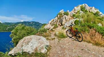 Şehir yaşamının stresinden uzakta, doğayla baş başa kalıp kendini tamamen &ouml;zg&uuml;r hissetmek ister misin? Eğer cevabın evet ise hemen bisikletini hazırla, ormanların arasından bazen denize bazen de g&ouml;llere &ccedil;ıkacak yolları arşınlamaya gidiyoruz. İşte T&uuml;rkiye&rsquo;nin en keyifli bisiklet rotaları! Hatırlatma: Bisikletinle seyahate &ccedil;ıkarken kask, dizlik, fener ve fosforlu yelek gibi seni koruyacak malzemeleri unutmaman gerektiğini zaten biliyorsundur ama ben yine de hatırlatmak isterim. Yollara &ccedil;ıkmadan &ouml;nce g&uuml;venliğini ve sağlığını garanti altına almayı sakın unutma! 1. Artvin- Trabzon Artvin-Trabzon bisiklet rotası, Karadeniz'in muhteşem doğası i&ccedil;inde yaklaşık 230 kilometrelik bir mesafeyi kapsar. Bisiklet&ccedil;iler genellikle bu rotayı &uuml;&ccedil;e b&ouml;lerek Trabzon-Rize, Rize-Hopa ve Hopa-Artvin şeklinde dolaşırlar. Rota yemyeşil &ccedil;ay tarlaları ve doğal g&uuml;zelliklerin arasından ge&ccedil;er. Orta zorlukta bir rota olarak değerlendirilir. Dağ ya da yol bisikleti tercih edebilirsin. Hava koşullarına dikkat etmek &ouml;nemli, &ouml;zellikle yağmurlu havalarda kaygan zeminlere dayanıklı tekerlekler tercih edilmeli. 2. Frig Vadisi Afyon, Ankara, Eskişehir ve K&uuml;tahya illerinin sınırlarının i&ccedil;inde bulunan Frig Vadisi, T&uuml;rkiye&rsquo;nin en uzun 3. y&uuml;r&uuml;y&uuml;ş yolu olan Frig Yolu&rsquo;na ev sahipliği yapıyor. 506 kilometre uzunlukta olan Frig Yolu, aynı zamanda T&uuml;rkiye&rsquo;nin en g&uuml;zel bisiklet rotalarından biri &ccedil;&uuml;nk&uuml; bu yol &uuml;zerinde g&ouml;receğin yapılar gezini unutulmaz bir deneyime d&ouml;n&uuml;şt&uuml;r&uuml;yor. Peribacaları, t&uuml;f kayalara oyulmuş kiliseler ve kaya mezarları gibi tarih&icirc; eserler boyunca pedal &ccedil;evirmek &ccedil;ok keyifli. Frig Yolu, derin vadilerden oluşan bir b&ouml;lgede ve &ouml;zellikle bisiklet sporuyla ilgilenen deneyimli bisiklet&ccedil;iler tarafından tercih edilir. Parkurlar farklı materyallerden oluşur, yani asfalt, toprak ve kum gibi y&uuml;zeylere sahip. Şehir bisikletleriyle kullanılabilecek rotalar olduğu gibi daha dayanıklı ara&ccedil;lara ihtiya&ccedil; duyulan yol ve dağ bisikleti rotaları da bulunur. Yeni başlayanlar veya kendine g&uuml;venmeyenler i&ccedil;in Frig Yolu zorlayıcı bir rota olabilir. Konum Linki 3. Kapadokya &Uuml;lkemizin en meşhur turizm cennetlerinden biri olan Kapadokya, balon turu ve ATV dışında bisiklet tutkunları i&ccedil;in de olanaklar sunuyor. Olduk&ccedil;a geniş bir b&ouml;lgeye yayıldığı i&ccedil;in &ccedil;ok keyifli rotalar sunan Kapadokya&rsquo;da kendini kısıtlamadan g&ouml;nl&uuml;n nereye isterse oraya pedal &ccedil;evirebilirsin. Daha uzun bir yolculuk i&ccedil;in G&uuml;vercinlik, Paşabağı, Kızıl&ccedil;ukur gibi vadiler arasını tercih edebilirsin. B&ouml;lgenin &ouml;nemli yerlerini g&ouml;rmek istersen Avanos ve Mustafapaşa arasındaki g&uuml;zerg&acirc;hta bisiklet s&uuml;rebilirsin. Bu b&ouml;lgelerdeki zorluk seviyesi biraz profesyonellik gerektirebilir, bu y&uuml;zden dağ bisikletiyle gitmek en iyisi. Ancak &Uuml;rg&uuml;p, G&ouml;reme, Ortahisar gibi yerlerdeki rotalarda şehir veya yol bisikletiyle kısa mesafeli s&uuml;r&uuml;şler yapabilirsin. Konum Linki {insightBoxStart}İpucu: En iyi otel fiyatlarını tek bir yerde g&ouml;rmek, se&ccedil;eceğin otel hakkında bilgi almak ve saniyeler i&ccedil;inde rezervasyon yapmak i&ccedil;in ENUYGUN'da otel araştırmasına başlayabilirsin.{insightBoxEnd} {hotel_search_form_banner} 4. Yenice Ormanları Karab&uuml;k'teki Yenice Ormanları bisiklet s&uuml;rmek isteyenler i&ccedil;in ideal bir rota. Yenice Ormanları, T&uuml;rkiye'nin en b&uuml;y&uuml;k blok ormanlarından biri ve 7 bisiklet parkuruna sahip. Parkurlar toprak yollar, dere ge&ccedil;işleri ve inişli &ccedil;ıkışlı rotalardan oluşuyor, bu nedenle dağ bisikletiyle pedal &ccedil;evirmek gerekiyor. Şehir bisikletiyle gelirsen bu parkurlar zorlayıcı olabilir, bu y&uuml;zden kamp alanları &ccedil;evresinde daha kolay bisiklet s&uuml;r&uuml;lebilecek rotaları tercih etmek daha iyi olabilir. Konum Linki 5. Hitit Yolu Hitit Yolu, Hattuşa ile Alacah&ouml;y&uuml;k arasında uzanan ve tarih meraklısı bisiklet severler tarafından tercih edilen bir rota. Bu yol, ge&ccedil;mişte kervan ve g&ouml;&ccedil; yolu olarak kullanılmış ve toplamda 6 farklı bisiklet rotasına sahip. Toplamda yaklaşık 406 kilometrelik bir uzunluğa sahip olan bu parkurlar, bazı b&ouml;lgelerde toprak, bazı b&ouml;lgelerde ise asfalt zeminli. Bu nedenle bu rotaları dağ bisikletiyle keşfetmek uygun olur. Dağ bisikletinle bu yolculuğa &ccedil;ıkarsan, &Ccedil;atak, Soğucak, Evci gibi kamp alanlarında dinlenmek i&ccedil;in &ccedil;adır kurabilirsin. {insightBoxStart}Yazar Notu: Eğer dağ bisikleti deneyimin yoksa, &ouml;nce dağ bisikleti konusunda kendini geliştirdikten sonra bu rotaları keşfetmeni &ouml;neririm.{insightBoxEnd} 6. Likya Yolu Likya Yolu &uuml;lkemizde trekkingin yanı sıra bisiklet tutkunları i&ccedil;in de harika bir deneyim sunan rotalardan. Fethiye'den Antalya'ya kadar uzanan bu yol, Akdeniz'in masmavi sularına karşı muhteşem bir manzara sunar. Bu 535 kilometrelik parkurda pedal &ccedil;evirmek i&ccedil;in b&uuml;y&uuml;k bir tutku gerektirir. Likya Yolu'ndaki parkur patika ve toprak yollardan oluştuğu i&ccedil;in dağ bisikletiyle yolculuk yapman &ouml;nemli. Dağ bisikletini aldıktan sonra kondisyonuna ve bisikletine en uygun rotayı se&ccedil;erek pedal &ccedil;evirmeye başlayabilirsin. Yol boyunca bir&ccedil;ok antik kent ve doğal g&uuml;zellik bulunması, hangi rotayı se&ccedil;ersen se&ccedil;in unutulmaz bir yolculuk deneyimi yaşamanı sağlayacak. Konum Linki 7. G&ouml;kova K&ouml;rfezi G&ouml;kova K&ouml;rfezi rotası bisiklet s&uuml;rerken &uuml;lkemizin g&uuml;zelliklerini keşfedebileceğin bir se&ccedil;enek. Bu rota Bodrum'dan başlayarak yaklaşık 295 kilometrelik bir mesafeyi kapsar ve Knidos Antik Kenti'nde son bulur. Muğla Bisiklet Derneği tarafından G&ouml;kova Bisiklet Turu da bu rota &uuml;zerinde d&uuml;zenleniyor. G&ouml;kova K&ouml;rfezi rotası, asfalt yollardan oluştuğu i&ccedil;in her t&uuml;r yol ve dağ bisikletiyle uyumlu bir rota olarak değerlendirilebilir. Ancak ince ve dişsiz lastikli bir bisikletle bazı noktalarda zorluk yaşayabilirsin. Konum Linki 8. K&ouml;pr&uuml;l&uuml; Kanyon Rafting ve trekking gibi birbirinden eğlenceli aktiviteleri yapabileceğin K&ouml;pr&uuml;l&uuml; Kanyon, aynı zamanda T&uuml;rkiye&rsquo;nin en keyifli bisiklet rotalarından biri. Minimum rakımın 163, maksimum rakımın ise 1167 metre olduğu i&ccedil;in havası tertemiz olan kanyon bisiklet yolculuğu i&ccedil;in orta-zor seviyesinde. Beşkonak&rsquo;tan başlayıp Selge&rsquo;ye kadar 11 kilometre boyunca devam eden yol tamamen asfalt. Bu yolda biraz tırmanış yapacaksın ama tırmanışın sonunda ulaşacağın manzara harika olacak. Yol Delisarnı&ccedil;&rsquo;a doğru devam edip Tazı Mevkii&rsquo;ne kadar uzanıyor. {insightBoxStart}Yazar Notu: Selge&rsquo;den sonraki yol boyunca toprak zemin olan kısımlar da var. Bu nedenle bu rota i&ccedil;in dağ bisikleti kullanmanı &ouml;neririz.{insightBoxEnd} Konum Linki 9. K&ouml;yceğiz-Ortaca-Dalaman Ekolojik bir rotada bisiklet s&uuml;rmek istersen doğru yerdesin. K&ouml;yceğiz-Ortaca-Dalaman rotası, The Eco Trails projesiyle 2018 yılında turizme kazandırılmış. Eko-turizme dikkat &ccedil;ekmek i&ccedil;in projelendirilen rota toplamda 700 kilometre uzunlukta. K&ouml;yceğiz&rsquo;de 5, Ortaca&rsquo;da 4, Dalaman&rsquo;da ise 5 tane g&uuml;zergah var. Eski yollar ve patikaları da i&ccedil;ine alan t&uuml;m bu g&uuml;zergahlar &uuml;zerinde uluslararası standartlara g&ouml;re hazırlanmış tabelalar bulunuyor. Bir&ccedil;ok doğal g&uuml;zelliği ve tarih&icirc; yolları g&ouml;rebileceğin rota, d&ouml;rt mevsimde de bisiklet s&uuml;rmek i&ccedil;in uygun. Konum Linki 10. Istranca Dağları Harika lezzetlerin tadına bakacağın bir bisiklet rotası arıyorsan Istranca Dağları tam sana g&ouml;re. Kırklareli&rsquo;nin Vize il&ccedil;esinde konumlanan bu rotada G&uuml;ng&ouml;rmez, Aksicim ve Balkaya k&ouml;ylerini ge&ccedil;eceğin bir yolculuk yapabilirsin. Rota boyunca iki kez sudan ge&ccedil;tiğin ve yollar bakir olduğu i&ccedil;in burası arazi s&uuml;r&uuml;ş&uuml;ne uygun dağ bisikletleriyle buraya gelebilirsin. Toplam 70 kilometre boyunca uzanan rota, g&uuml;n&uuml;birlik bir s&uuml;r&uuml;ş keyfi yaşamak i&ccedil;in ideal. Pedal &ccedil;evirdikten sonra Balkaya K&ouml;y&uuml;&rsquo;ndeki alabalık tesisinde balıkların tadına bakmak da t&uuml;m yorgunluğunu alıyor. Konum Linki {{campaignsSlider}} 11. Sapanca Sapanca 2020 D&uuml;nya Dağ Bisikleti Şampiyonası'na ev sahipliği yapmış ve bisiklet sporuna b&uuml;y&uuml;k &ouml;nem verilen yerlerden. Ay&ccedil;i&ccedil;eği Bisiklet Vadisi, belediye &ccedil;alışmalarıyla a&ccedil;ılmış ve hem d&uuml;nya şampiyonalarına ev sahipliği yapması hem de turistlerin ilgisini &ccedil;ekmesiyle bilinir. Sapanca G&ouml;l&uuml; &ccedil;evresinde de bisiklet s&uuml;rmek olduk&ccedil;a keyifli. G&ouml;l etrafındaki yollar, her t&uuml;r bisiklete uygun ve kolay bir s&uuml;r&uuml;ş imk&acirc;nı sunar, dağ bisikletine ihtiya&ccedil; duymazsın. Sapanca'da bisiklet, yerli halkın g&uuml;nl&uuml;k hayatının bir par&ccedil;ası olması i&ccedil;in &ccedil;alışmalar yapılan bir spor olarak g&ouml;r&uuml;l&uuml;r. Konum Linki 12. Belgrad Ormanı Biraz da şehir i&ccedil;inde k&uuml;&ccedil;&uuml;k bir hafta sonu ka&ccedil;amağı yapılacak bir rotadan bahsedelim değil mi? İşte tam da bunu derken aklına Belgrad Ormanı geldi eminim. Belgrad Ormanı i&ccedil;in İstanbul&rsquo;un akciğerleri dersek abartmış olmayız. Bir&ccedil;ok İstanbullunun hafta sonları temiz hava alıp doğayla i&ccedil; i&ccedil;e olmak i&ccedil;in tercih ettiği ormanda pedal &ccedil;evirmek de &ccedil;ok keyifli.Yaklaşık 20 kilometrelik parkuru şehir bisikletinle turlayabilirsin. Eğer yanına piknik malzemelerini alırsan parkuru tamamladıktan sonra k&uuml;&ccedil;&uuml;k bir piknikle kendini &ouml;d&uuml;llendirebilirsin. Konum Linki T&uuml;rkiye'nin en keyifli bisiklet yollarını keşfettikten sonra İstanbul'a yakın en iyi trekking rotaları yazımızı inceleyebilirsin.