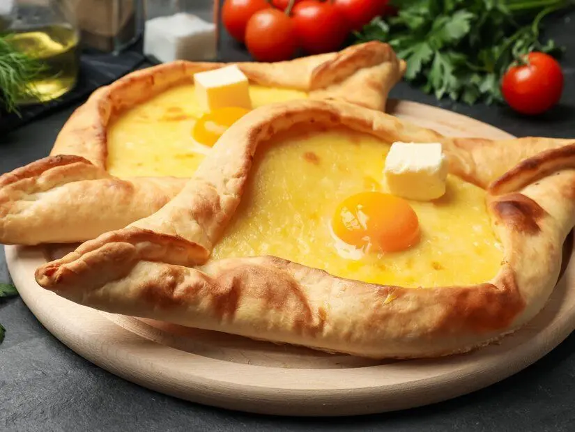 Peynirli, yumurtalı ve siyah masadaki diğer ürünlerle dolu lezzetli hachapuri