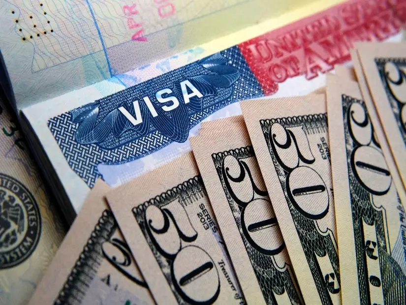 Pasaportta görülen ABD vize etiketi ve üzerine yerleştirilmiş dolar banknotları. 