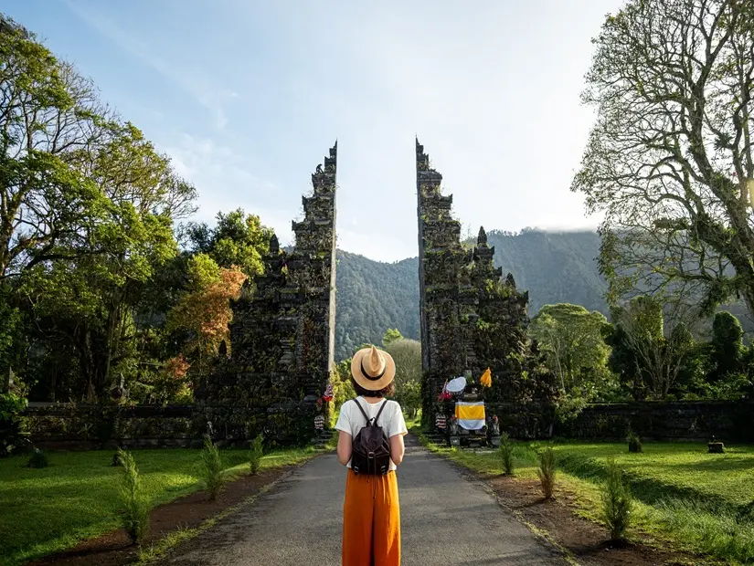 Sırt çantalı kadın turist gezgin Asya'daki tatilinde Bali Hindu tapınağında yürüyüşün tadını çıkarıyor