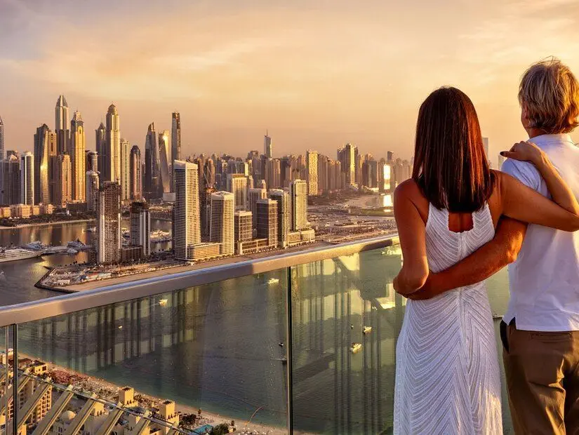 Birbirine sarılan bir çift, BAE'deki Dubai Marina'nın panoramik gün batımı manzarasının tadını çıkarıyor