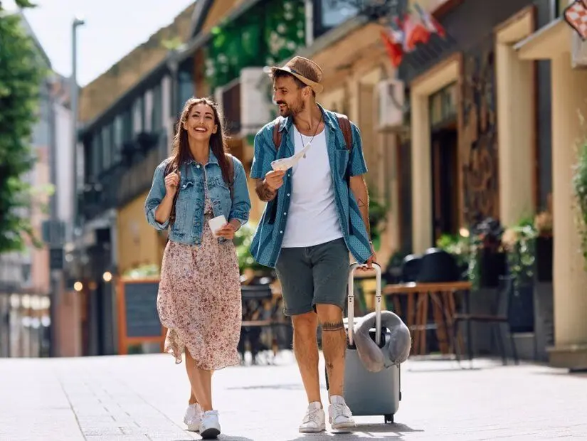 Birlikte seyahat ederken şehirde yürüyen mutlu turist çifti