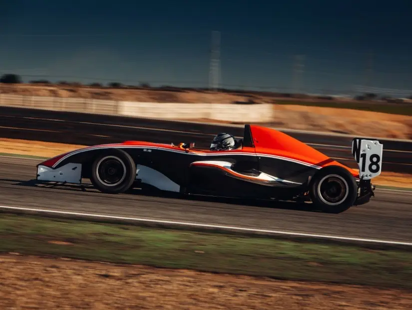 Formula 1 arabası gün batımı sırasında yarış pistinde hızlı gidiyor