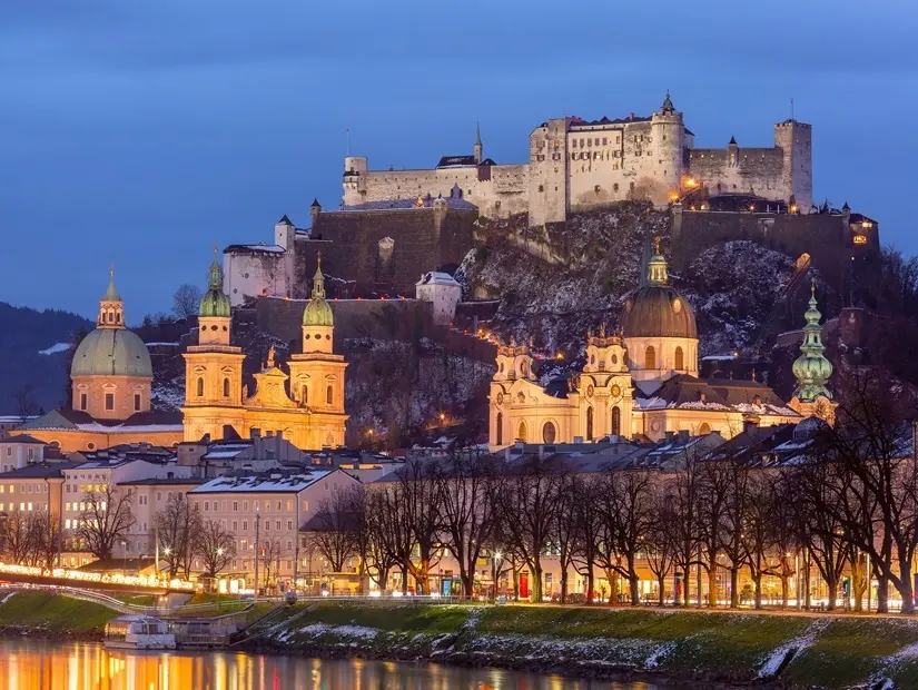 Avusturya'daki Salzburg'un Hohensalzburg Kalesi ve Salzburg Katedrali ile gün batımı manzarası.