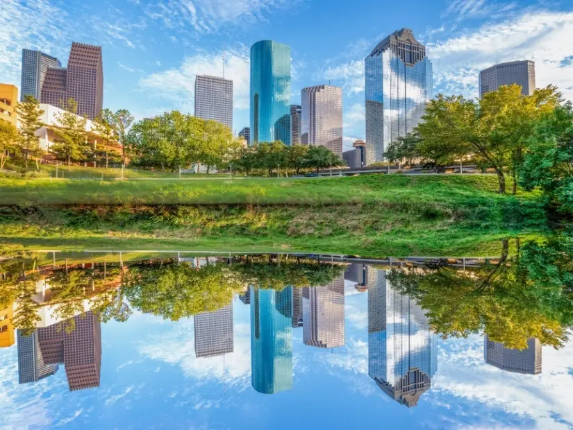 Buffalo Bayou parkından görülen sabah ışığında Houston, Teksas'ın doğal silueti ve nehirdeki yansıma
