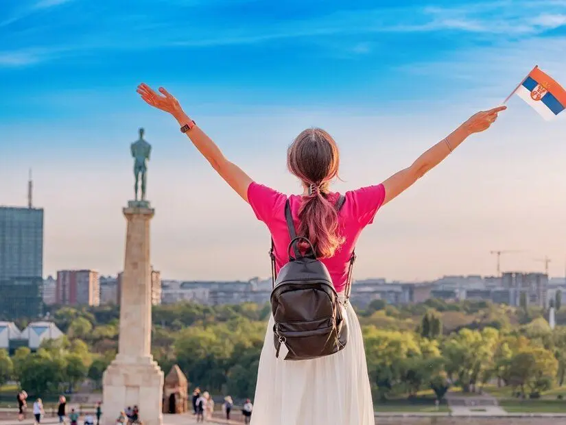 Sırt çantası ve Sırp bayraklı turistler, günbatımında Kalemegdan Kalesi'nden Belgrad şehir manzarasının keyfini çıkarıyorlar