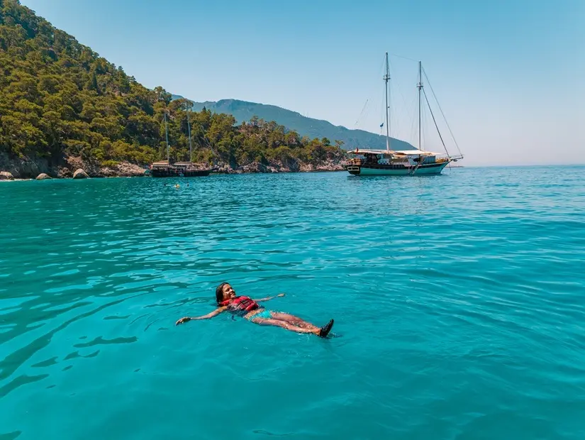 Türkiye'nin Fethiye kentinde okyanusta Kelebek Plajı'na tekne gezisi yapan genç kadın