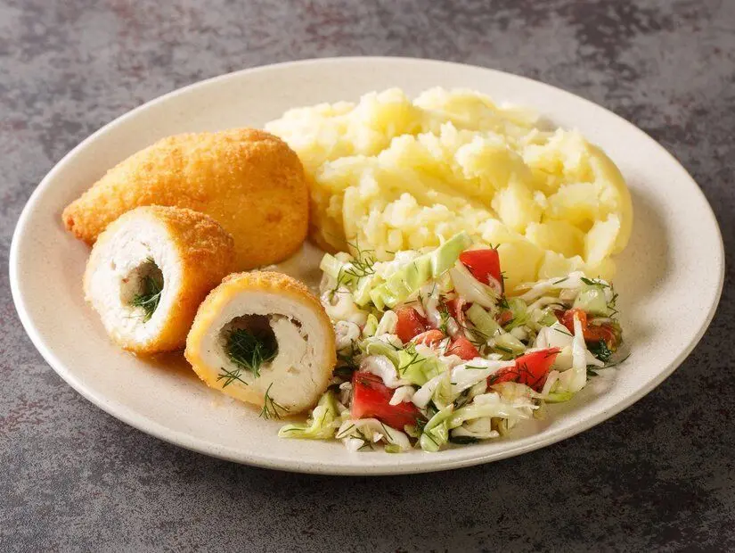 Masada tabakta servis edilen Kiev usulü tavuk , salata ve patates püresi