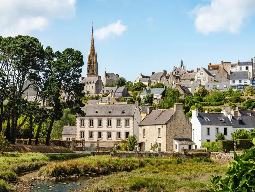 Brittany'de Pont-Croix Fransız köyü, sakin bir nehir boyunca, Goyen, tarihi taş evler, gür bahçeler ve baskın bir kilise kulesine sahiptir.