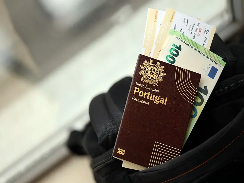 Portekiz pasaportu, turistik sırt çantasında para ve uçak biletleri ile yakın çekim