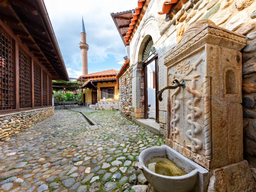 Arka planda Halveti Tekke Camii minaresi bulunan eski çeşme