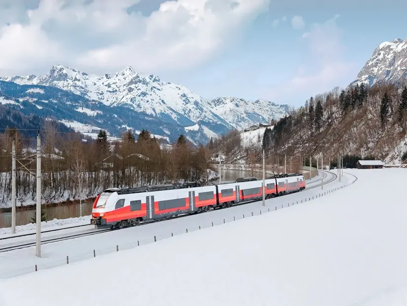 Avusturya'nın Salzburg kentindeki Pongau Bölgesi'ndeki Pfarrwerfen'de soğuk bir kış gününde, arka planda Alp dağlarının bulunduğu, yoğun karla kaplı vadide, Salzach Nehri kıyısındaki bir demiryolu kıvrımından geçen bir tren.