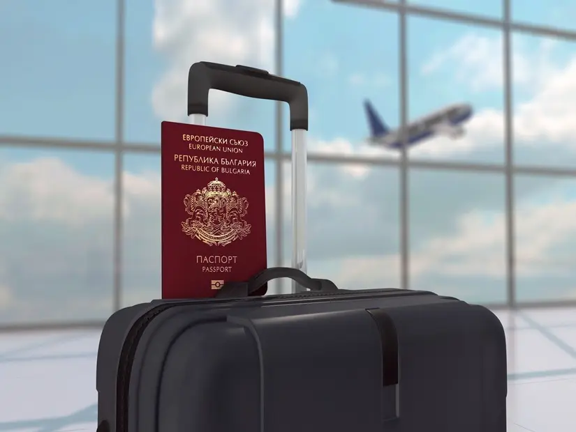 Siyah Bagaj Çantası Üzerinde Bulgaristan Pasaportu ve kalkış yapan bir uçağın bulunduğu odak dışı bir havaalanı arka planı
