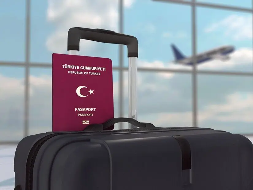 Siyah Bagaj Çantasında Türkiye Pasaportu ve kalkış yapan bir uçağın bulunduğu odak dışı bir havaalanı arka planı