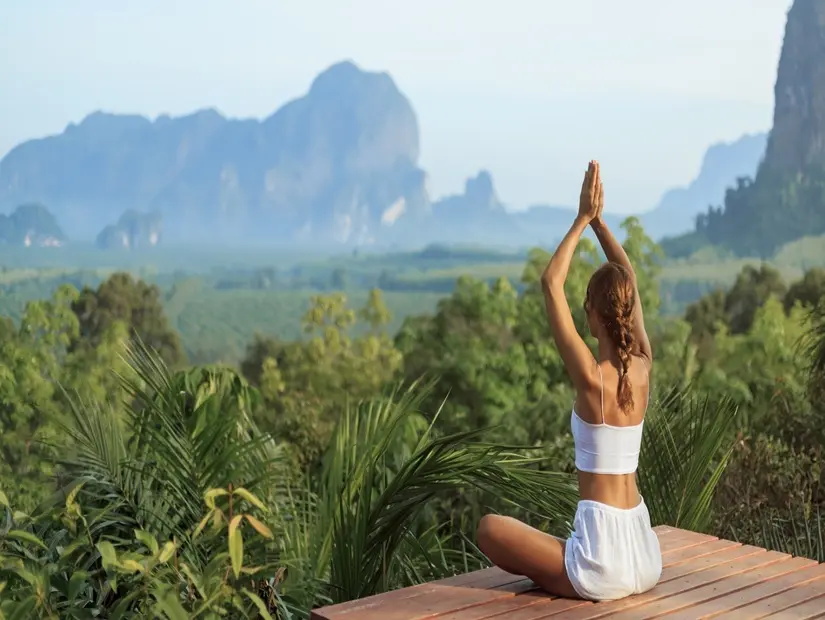 Tayland'ın Krabi şehrinin gür ormanı ve kireçtaşı kayalıklarına karşı yoga yapan kadın