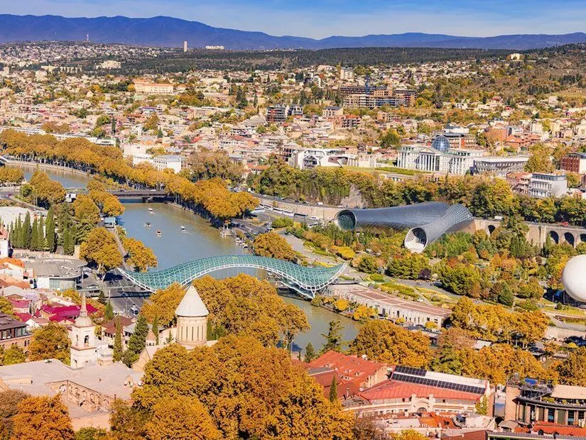 Tiflis, Gürcistan'ın sonbahar aylarında Kura nehri ve Rike Parkı'nı mavi bir gökyüzü altında gösteren panoramik manzara
