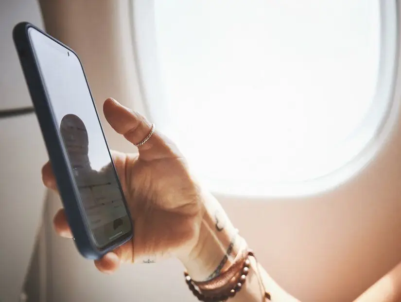 Eller, telefon ekranı ve yolculuk, biniş kartı veya uçuş detaylarını kontrol etmek için uçaktaki kişi