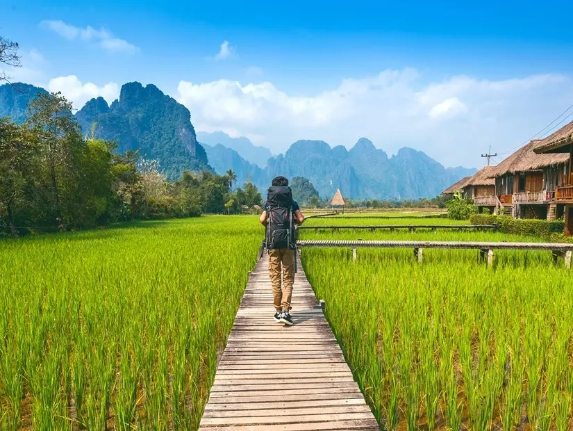 Laos'ta Vang Vieng'de ahşap yolda sırt çantalı yürüyüş turizmi.